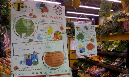 Le locandine della terza edizione di Tutti a Tavola!! Aggiungi un ospite anche tu, che prosegue oggi in cinque mercati coperti del Comune di Milano. Cinque grandi chef hanno pensato ad altrettanti menu da 3 portate calcolate per 4 persone e dal costo non superiore ai 20 euro. Tutti i contributi raccolti verranno trasformati a fine giornata in prodotti freschi di pari valore economico e destinati alle associazioni di volontariato