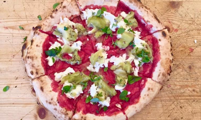 La squisita pizza con salsa di barbabietola, kiwi, bufala e trito di timo, maggiorana, basilico