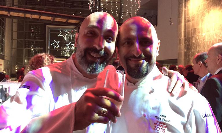 Due neo-stellati separati alla nascita e premiati dalla Michelin nella stessa edizione della guida, quella 2016, presentata la mattina e festeggiata la sera nella sede milanese della Mercedes Benz giovedì 10 dicembre. A sinistra, con un calice di champagne in mano, Andrea Ribaldone, radici milanesi e alessandrino di adozione, chef-patron dei Due Buoi in centro ad Alessandria, e resident chef di Identità Golose nei sei mesi di Expo. A destra Filippo Gozzoli che in un anno è riuscito dove Nobu mai in quindici: portare la stella da Armani in via Manzoni a Milano. Al ristorante di cucina italiana ovviamente. Per il gruppo fodnato e guidato da Giorgio Armani un colpaccio a livello mediatico