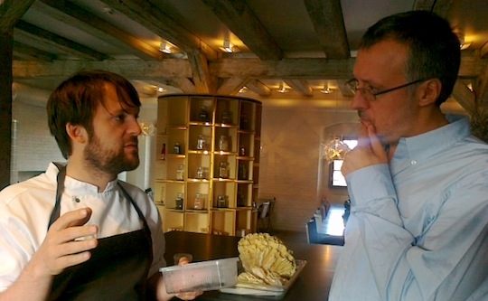 Galleria fotografica






In cammino verso il Noma. Il ristorante è al piano terra del palazzone più a sinistra. Per arrivarci dalla popolare insenatura di Nyhavn (il punto da cui è scattata la foto), occorre fare un bel giro. Ma si notano i lavori per la costruzione di un ponte. Che condurrà dritto all'insegna








Altra prospettiva sul Noma da Nyhavn. Il ristorante galleggia sulla Christianshavn, una delle tante isole artificiali che compongono Copenhagen








Di là del fiume, sulla lunga via che conduce allo spiazzo del Noma








Uno scenario molto tranquillo, di case pastello. Il silenzio è perché vanno tutti in bici













Al massimo si sente rombare qualche scafo








Il vascello davanti al Noma. Oltre a quella danese, sventolano le bandiere di Isole Far Oer e Groenlandia: le loro ambasciate sono nello stesso palazzo del ristorante. Coerenza nordica








Il retro del ristorante. L'80% delle 80 persone che lavorano al Noma viene a lavorare in bici, chef incluso








Dietro al ristorante, un'iscrizione ricorda i passeggeri scomparsi a bordo della danese Hans Hedtoft. Il transatlantico si scontrò il 30 gennaio 1959 contrò un iceberg in Groenlandia. Fu ritrovata solo una cintura di sicurezza
 








L'ingresso del ristorante, al civico 93 di Strandgade








La vista, ingresso alle spalle








Tra l'ingresso e la cucina a vista, spicca un corner di decoro simil-giapponese. A sinistra s'intravede Noma, time and place in Nordic Cuisine, edizioni Phaidon, un testo fondamentale per approfondire tutti i rivoli del Redzepi-mondo. La versione italiana si ordina qui








Una pianta di piccoli agrumi orla la cucina a vista








La porta d'ingresso vista dalla cucina








Le sedie, molto comode, sono anni Sessanta con schienali foderati di pelle di pecora, alcune più morbide di altre








I tavoli sono ampi e senza tovaglie. Attorno prevale il grigio e i colori rustici, sulle travi in legno del soffitto ma anche sulle divise dei ragazzi di sala








La finestra accanto al nostro tavolo








E' lo chef Rene Redzepi a introdurci al pasto: in un vaso di fiori danesi, l'unico pendaglio commestibile è una sorta di carta musica croccante (flatbread) di farina di malto all'aroma di ginepro. Nel piattino in basso, una deliziosa crème fraîche acida per intingerlo








Il flatbread è quello che svetta. "Ma se ci tenete, provate a mangiare anche i fiori", scherza Redzepi. Il cuoco scompare nelle segrete del Noma. Lo ritroveremo solo alla fine del pasto








Tutti i 14 appetizer si mangeranno con le mani. Unica posata, il coltello per tirar su e leccare la crème fraîche da sola (da fare quando tutti gli altri clienti son distratti, però)








Moss and Cep: Muschio di renna con polvere di funghi porcini. E' il corpo bianco, molto saporito ed evanescente, da intingere anch'esso nella crème fraîche
 








Crispy pork skin and black currant: Pelle di maiale croccante e ribes nero, lo strato più esterno. Aspro e croccante








Il ribes nero non ci lascerà prima di molto tempo








Blue mussels and celery: cozze e sedano. Solo due sono quelle buone








La parte inferiore del guscio è commestibile (ancora farina di malto)








Il quinto appetizer è nascosto in una deliziosa scatola di biscotti in latta della tradizione danese (chi non ricorda i Danish butter cookies?)








Cinque tondini, ma solo due "interessanti"








Si chiamano Cheese cookies, rocket and stems, letteralmente Biscotti al formaggio, ruchetta e gambi di erbe aromatiche, un felice snack potenzialmente riproducibile nei nord e nei sud del mondo








Appetizer #6: Potato and duck liver, Patate e fegato d'anatra: le patate croccanti sono in due strati e a mo' di sandwich racchiudono la mousse di fegato. La spolverata è di funghi trombette dei morti, disidratati e polverizzati, una tecnica che troveremo frequentemente








Dried carrot and sorrel, Carote grigliate a fuoco lento per 14 ore, disidratate e servite su polvere di fieno. Si intingono nell'emulsione di acetosella accanto. Un grande piatto perché di inattesa, energica acidità








Ottava entrée: Caramelized milk and cod liver, Biscotto di latte caramellato e fegato di merluzzo, quest'ultimo ghiacciato e pulito. Il secondo dona un aroma molto strong, che domina sul biscotto croccante. Per palati muscolari








Le uova dentro l'uovo








Pickled and smoked quails eggs, Uova di quaglia sbollentate, marinate e affumicate, un classico del Noma. Il tuorlo è completamente liquido








Col Veal fibres and söl, Filamenti di vitello e söl, decimo appetizer, entra in gioco per la prima volta un'alga di mare. E' il söl, appunto, dulse in inglese, Palmaria palmata nella tassonomia scientifica, un'alga rossa incastrata nei filamenti di vitello precedentemente tagliati sottili e poi fritti. Curioso l'impiatto a nido di ingredienti che alla fine incastrano terra e mare








Herb Toast and smoked cod roe, Toast alle erbe e uova di merluzzo affumicato, un'altra grandiosa tapa nordica da far su in due bocconi. Se non ricordiamo male, lo strato superiore è brodo di fegato d'anatra disidratato








Radish, soil and grass, Rapanello, "suolo" ed erba, un altro grande classico del Noma, un paesaggio commestibile di chiara genesi basca-adrianesca, molto replicato negli anni. Carote baby e rapanelli sono interrati in un "suolo" che è una crema di farina di malto con nocciole disidratate. Sotto ancora, uno yogurt di erbe. Finite le verdure, abbiamo chiesto dei cucchiaini per ripulire il suolo








Una foto (di spreadbutter) chiarisce meglio il contenuto del vasetto








Æbleskiver e muikku, penultimo appetizer, di concezione piuttosto recente. Un'antica tradizione dolce danese (Æbleskiver significa "piccoli pezzi di mela" ma la mela qui non c'è) è presentata in versione salata. Code e teste dei muikku, sorta di aringhe baby, sono infilzate in due bigné dall'impasto molto morbido con del ripieno di cetriolo marinato, ben riconoscibile al palato. L'aspetto dispone il cliente alla sfida ma la sua bizzarria visiva si scioglie presto in due bocconi morbidi, eleganti e deliziosi








Ultimo di 14 appetizer: Sorrel leaf and cricket paste, Foglia di acetosella (leggermente piccante) con pasta di grillo. Sì, proprio l'insetto dei prati, qui in consistenza di crema, inserita nel gambo dell'acetosella. Mettendo a fermentare grilli e orzo fermentato, Redzepi ha ottenuto una sorta di garum molto interessante, simile alla soia. Completa il piatto in foto, una granita di nasturzio ghiacciato








E il vino? Non producendo la Danimarca nettari di rilievo, è forse il capitolo meno allettante del Noma. La carta è un trionfo di vini ottenuti in climi freddi: francesi, tedeschi o austriaci soprattutto. Vini di acidità spinta che si combinano bene con le prevalenti acidità dei piatti. Le persone inquadrate nella foto hanno optato per il pairing coi succhi di frutta, quelli sì interessanti e autoctoni: il percorso prevede 7-8 succhi tra cui carote e ginepro, sedano e sedanorapa, cetriolo, eccetera. E i vini italiani? Pochi e tutti rossi, soprattutto di produttori di nebbiolo del Piemonte. "Ma li chiedono solo i norvegesi", ci raccontano








Terminati appetizer e main courses, sbirciamo i lavori in cucina. In primo piano, Samuel Nutter, sous chef inglese








Al centro, riconosciamo Matthew Orlando di San Diego, 35 anni e da 4 e mezzo head chef del Noma. Più tardi ci rivelerà che entro un paio d'anni aprirà il suo ristorante a Copenhagen. "E Renè che ne pensa?", chiediamo. "E' proprio lui a incoraggiarci a metterci in proprio", risponde Orlando. Vero, chiedere anche a Christian Puglisi








Ancora Orlando ci spiegherà che, tra sala, cucina, preparazioni e laboratorio, il Noma arriva a impiegare dall'alba a mezzanotte fino a 80 persone








La cucina prevede 7 comparti: il caldo, il freddo, la pasticceria, gli snack, produzione e mise-en-place, le preparazioni della squadra del mattino e la ricerca (su quest'ultima torneremo più avanti). Gli stagisti scelgono di lavorarci, sapendo di non essere pagati. Redzepi riceve un centinaio di curricula a settimana








Torniamo a tavola e troviamo nuove posate: rami appuntiti di sambuco








Servono a infilzare il primo delle portate "serie", Potato and snails, patate e lumache, servito in due piatti. Il primo è una terrina (rovente) di piccole deliziose patate affumicate e semiaffogate in una salsa al burro dolce e al tavolo spolverate con sale proprio di sambuco. Accanto, piccoli ceppi d'albero affumicati








Accanto, l'altra metà del piatto da infilzare coi bastoncini di sambuco: lumache glassate nel loro succo con burro dolce, olio al prezzemolo ed emulsione di piselli fermentati








Dopo 15 portate arrivano le posate. "Si torna alla civiltà", scherza il ragazzo di sala








...e arriva pure il pane, nascosto in una stoffa soffice con accanto due ciotoline che contengono burro da latte di capra e burro di grasso e crumble di maiale. Colesterolemici, vade retro








Solleviamo la stoffa: il pane è una pagnotta di lievito naturale di grano locale. La crosta è super-fragrante e il cuore molto sofficie e poroso








Cooked fava beans and beach herbs, Fave stufate gentilmente ed "erbe di spiaggia" (che poi sono diversi tipi di alghe di mare). Le fave sono fantastiche nella loro compattezza inaspettatamente dolce








Con la terza portata del ciclo "serio" veniamo ai ragazzi di sala: sono tutti molto professionali ma anche rilassati. Tra i 30 e i 40 anni, molti tatuati, ruotano di continuo al nostro tavolo: una trentina dei piatti sono stati serviti e illustrati da 10 camerieri diversi, molti dei quali cuochi dei livelli più alti della gerarchia. Il ragazzo in foto che ci serve Berries and cucumber, Bacche e cetrioli, si chiama Beau Clugston, è australiano e da poche ore è un nuovo sous-chef del Noma








Ai frutti di bosco e insalata di cetrioli si unisce del succo di camomilla...








...et voilà








Insalata di brown crab (granchi atlantici), tuorlo d'uovo, erbe di campo e il rosso sono le uova del granchio. I ragazzi si raccomandano di fare attenzione perchè potrebbe esserci del carapace o delle chele: la carne del granchio è stata rimossa tutta a mano. Noi ci scontriamo solo con un fresco schiaffo iodato








Accanto alle langoustine, scampi norvegesi, torna l'alga söl, questa volta in forma di emulsione con acqua di ostriche. I puntini rossi sono segale disidratata








Cavolfiore e pino, crema e rafano. Pensi a una capasanta e invece è un trancio di cavolfiore quello che spunta da sotto gli aghi di pino. E' ricavato dalla parte alta dell'ortaggio, arrostito a arricchito con gli aromi di pino, abete, ginepro e rafano. L'orto e il silvestre








Lucioperca con gambi di verdure. Impeccabile ma insolitamente classico nella sua concezione su salsa al burro e capperi. Incuriosisce la disposizione, che lascia intonsa più di metà del piatto. Come a voler lasciar libero il lucioperca di sguazzare di nuovo








Arrivano in tavola nuovi oggetti: olio di fieno e un cronometro. E' l'inizio del gioco di The hen and the egg, La gallina e l'uovo








The hen and the egg #2: attorno a un tegamino rovente su del fieno appena umido, notiamo una chips a spirale di patata e un uovo (d'anatra, ci dicono)








The hen and the egg #3: accanto al tegame, foglie di spinaci, aglio selvatico, germogli e fiori di campo vari








The hen and the egg #4. "Dovete rompere voi l'uovo e cuocerlo", ci spiegano armati di olio di fieno, che spruzzeranno nel tegame prima del nostro esercizio








The hen and the egg #5: son riuscito a non sbrodolare. Il piatto, spiegherà Redzepi poi, "E' un po' un invito sdrammatizzante a cucinare. Sono rimasto sorpreso dal fatto che tanti clienti non hanno mai rotto un uovo. Cerco di mostrare loro che la cucina è in fondo un esercizio molto elementare"








The hen and the egg #6: dopo 120 secondi esatti di cronometro, si uniscono all'uovo le verdure e si rimesta il tutto








The hen and the egg #7: tocco finale, una salsa di acetosella. Il piatto non è memorabile...








...ma il risultato è lo stesso delle 21 portate precedenti: piatto spazzolato The hen and the egg #8








Animelle di vitello, erbe di campo, funghi e sedanorapa. Un gran piatto, ma non esattamente quello che ti aspetti al Noma. Sottigliezze eh








A un passo dai dolci, il brusio in sala si fa più sostenuto. L'alcol e le discussioni sull'incredibile girandola di piatti provati








E il brusio lievita ancora al primo dei due dolci: Blueberries and ants, Mirtilli e formiche (la foto è di garyalanfine, avevo terminato le batterie). Il piatto è duplice: la foto mostra la prima metà, che racchiude una confettura di formiche tra due foglie di nasturzio. Ce la porta al tavolo Rosio Sanchez da Chicago, splendida coordinatrice dei dessert del Noma. E le formiche? Ci torniamo alla fine della gallery








Mirtilli e formiche parte seconda: accanto alle foglie di nasturzio con formiche, arriva un geniale sandwich con gelato di mirtilli (la foto è ancora di garyalanfine)








Ventiquattresimo e ultimo piatto, un "classico" Gammel Dansk, sorta di Jaegermeister danese qui sposato ad acetosella e latte disidratato. Apprezziamo la voglia di non sovraccaricare con ulteriori bombe al cioccolato o altre grasse cremosità che a fine pasto chiederebbero gli straordinari ai succhi gastrici (grazie ancora a garyalanfine)








Dopo oltre 3 ore di degustazione, ci si accomoda tutti nel dehors accanto: in vetrina spiccano grappe di Brunello








Potevano farti mancare lo skyr, il formaggio fermentato acido degli islandesi? Certo che no: agli albori della New Nordic Cuisine venne praticamente brandito da Redzepi come simbolo delle rivoluzione. L'arma per contrastare il dilagare dei formaggi francesi in Danimarca, così come l'olio di colza in vece dell'olio d'oliva








Riordinata la sala per la sera, Kim Sander e Matthew Orlando ci invitano a fare un sopralluogo nei back office del Noma








I ragazzi si divertono ma il lavoro è un massacro: tra il pranzo e la cena ci sono solo 45 minuti di pausa, dalle 17 alle 17.45. "Per questo", spiega Redzepi, "è fondamentale tenere chiuso due giorni, domenica e lunedì. Così stacchiamo da ogni pensiero. 7 su 7 sarebbe controproducente per l'umore di tutti"








Orlando ci mostra il gazebo all'aperto sul retro, dove si griglia e affumica qualsiasi cosa








Al primo piano, un tavolo da 9-15 persone che si aggiunge ai coperti del piano terra. "E' il nostro table's chef' , dice Orlando








Alle pareti, una felice riproduzione caricaturale della cucina di sotto








Nella sala accanto, uno squadrone di giovanissimi è perennemente alle prese con le pre-preparazioni








Tagliare, separare, sgusciare, sminuzzare...








Il terzo ambiente al primo piano è la sala del relax dei ragazzi...








...ma anche quella del grande capo...








...che infatti troviamo defilato ad affettare un mega-cavolo...








...che cavolo non è: "E' un fungo", rivela Renè Redzepi, "un regno che mi affascina tantissimo perché è vasto così", dice disegnando un cerchio molto ampio con le braccia, "mentre noi ne sappiamo tanto così", mima chiudendo pollice e indice. "Purtroppo questa stagione non è propizia per i funghi, troppo secca, ma non dispero"








Ma parliamo di formiche. Redzepì tira fuori un tupperwear brulicante di insetti che vagano rintontiti. "Non è questione di stravaganza o sensazionalismo", spiega, "occorre solo infrangere i nostri tabù, non come esercizio fine a se stesso, ma come esplorazione di tutti i flavour possibili"








"Senti che effluvi naturali di cardamomo escono da qui? Le formiche li rilasciano in modo del tutto naturale per tenere lontani i nemici", spiega








La sera stessa ci scrive su twitter la giornalista spagnola Julia Perez da Lima, spiegando che gli insetti amazzoni che cucina il cuoco venezuelano Sumito Estévez sanno invece di limone
 





