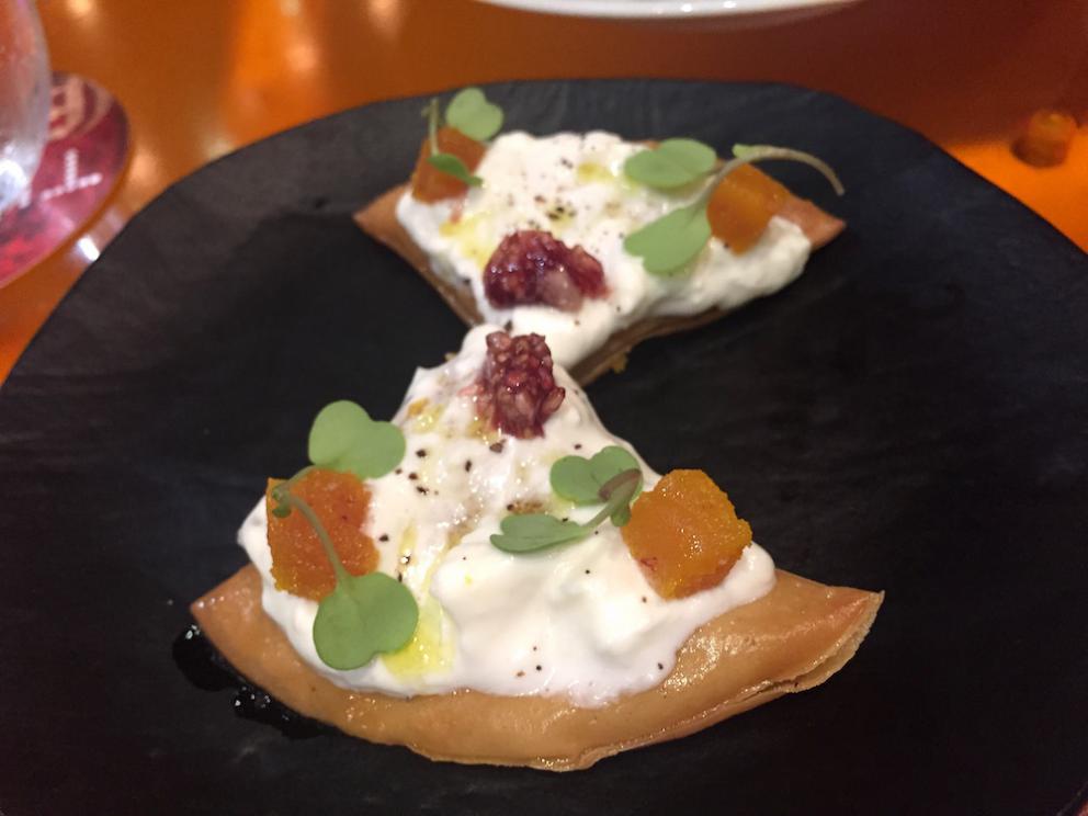 Galleria fotografica






Consommè de garbanzos. Prima che cominci il menu degustazione, viene portata al tavolo una bottiglia di vetro contenente del brodo freddo di ceci (in alto a destra). Ventitrè piatti dopo, alla fine del percorso "salato", verrà versato, in un bicchierino da grappa, del brodo caldo di jamon iberico da una teiera. Sopra ancora, la schiuma del brodo di ceci. Un caldo-freddo speciale (foto @ticketsbar instagram)









Tosta de pollo y anchoa. Primo piatto: toast di pelle di pollo con lisca di acciuga. A lato, una crema di acciughe composta da burro e pasta di acciughe









Olive Gordal. Uno dei simboli della saga Adrià: le olive sono immerse in un liquido d'olio extravergine d'oliva, cannella, buccia di limone e anice stellato. Si tirano su con un cucchiaino forato, si poggiano su una conchiglia di legno a lato e da qui in bocca. Gordal è una varietà dall'Andalusia









Prima preparazione rifinita al tavolo: Polo de almendras









Polo de almendras è uno stecco di gelato al latte di mandorle, spennellato sul posto con olio d'oliva e cosparso con granelle di mandorle, fiori di sambuco e sale. E' servito su un piatto con cubetti di ghiaccio. Dolce(salato) e gelato all'inizio del pasto e non alla fine, uno schema molto Adrià









Coliflor y caviar. Ganache di cavolfiore e caviale russo Schrenkii









Gamba a la sal fría. Gamberi marinati nel tè Lapsang Souchong con zest di bergamotto. Sono serviti su un vassoio con "neve di sale" per ricordare il ghiaccio tipico di un mercato del pesce









Atún con cerezas. Tonno e ciliegia: ventresca di tonno confit in grasso di prosciutto, accompagnata da una ciliegia affumicata (senza nocciolo)









Ceviche de melón cantaloup. Ceviche di melone cantalupo con succo di lime, coriandolo e leche de tigre di kumquat. Servito con kumquat, olio di coriandolo e neve di kumquat. Citrico alla terza






