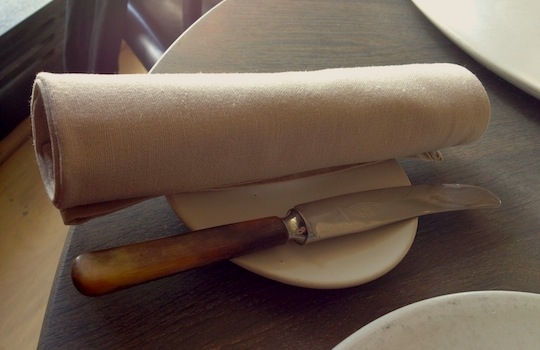 Galleria fotografica






In cammino verso il Noma. Il ristorante è al piano terra del palazzone più a sinistra. Per arrivarci dalla popolare insenatura di Nyhavn (il punto da cui è scattata la foto), occorre fare un bel giro. Ma si notano i lavori per la costruzione di un ponte. Che condurrà dritto all'insegna








Altra prospettiva sul Noma da Nyhavn. Il ristorante galleggia sulla Christianshavn, una delle tante isole artificiali che compongono Copenhagen








Di là del fiume, sulla lunga via che conduce allo spiazzo del Noma








Uno scenario molto tranquillo, di case pastello. Il silenzio è perché vanno tutti in bici













Al massimo si sente rombare qualche scafo








Il vascello davanti al Noma. Oltre a quella danese, sventolano le bandiere di Isole Far Oer e Groenlandia: le loro ambasciate sono nello stesso palazzo del ristorante. Coerenza nordica








Il retro del ristorante. L'80% delle 80 persone che lavorano al Noma viene a lavorare in bici, chef incluso








Dietro al ristorante, un'iscrizione ricorda i passeggeri scomparsi a bordo della danese Hans Hedtoft. Il transatlantico si scontrò il 30 gennaio 1959 contrò un iceberg in Groenlandia. Fu ritrovata solo una cintura di sicurezza
 








L'ingresso del ristorante, al civico 93 di Strandgade








La vista, ingresso alle spalle








Tra l'ingresso e la cucina a vista, spicca un corner di decoro simil-giapponese. A sinistra s'intravede Noma, time and place in Nordic Cuisine, edizioni Phaidon, un testo fondamentale per approfondire tutti i rivoli del Redzepi-mondo. La versione italiana si ordina qui








Una pianta di piccoli agrumi orla la cucina a vista








La porta d'ingresso vista dalla cucina








Le sedie, molto comode, sono anni Sessanta con schienali foderati di pelle di pecora, alcune più morbide di altre








I tavoli sono ampi e senza tovaglie. Attorno prevale il grigio e i colori rustici, sulle travi in legno del soffitto ma anche sulle divise dei ragazzi di sala








La finestra accanto al nostro tavolo








E' lo chef Rene Redzepi a introdurci al pasto: in un vaso di fiori danesi, l'unico pendaglio commestibile è una sorta di carta musica croccante (flatbread) di farina di malto all'aroma di ginepro. Nel piattino in basso, una deliziosa crème fraîche acida per intingerlo








Il flatbread è quello che svetta. "Ma se ci tenete, provate a mangiare anche i fiori", scherza Redzepi. Il cuoco scompare nelle segrete del Noma. Lo ritroveremo solo alla fine del pasto





