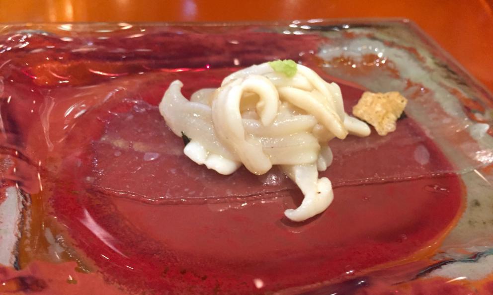 Galleria fotografica






Consommè de garbanzos. Prima che cominci il menu degustazione, viene portata al tavolo una bottiglia di vetro contenente del brodo freddo di ceci (in alto a destra). Ventitrè piatti dopo, alla fine del percorso "salato", verrà versato, in un bicchierino da grappa, del brodo caldo di jamon iberico da una teiera. Sopra ancora, la schiuma del brodo di ceci. Un caldo-freddo speciale (foto @ticketsbar instagram)









Tosta de pollo y anchoa. Primo piatto: toast di pelle di pollo con lisca di acciuga. A lato, una crema di acciughe composta da burro e pasta di acciughe









Olive Gordal. Uno dei simboli della saga Adrià: le olive sono immerse in un liquido d'olio extravergine d'oliva, cannella, buccia di limone e anice stellato. Si tirano su con un cucchiaino forato, si poggiano su una conchiglia di legno a lato e da qui in bocca. Gordal è una varietà dall'Andalusia









Prima preparazione rifinita al tavolo: Polo de almendras









Polo de almendras è uno stecco di gelato al latte di mandorle, spennellato sul posto con olio d'oliva e cosparso con granelle di mandorle, fiori di sambuco e sale. E' servito su un piatto con cubetti di ghiaccio. Dolce(salato) e gelato all'inizio del pasto e non alla fine, uno schema molto Adrià









Coliflor y caviar. Ganache di cavolfiore e caviale russo Schrenkii









Gamba a la sal fría. Gamberi marinati nel tè Lapsang Souchong con zest di bergamotto. Sono serviti su un vassoio con "neve di sale" per ricordare il ghiaccio tipico di un mercato del pesce









Atún con cerezas. Tonno e ciliegia: ventresca di tonno confit in grasso di prosciutto, accompagnata da una ciliegia affumicata (senza nocciolo)









Ceviche de melón cantaloup. Ceviche di melone cantalupo con succo di lime, coriandolo e leche de tigre di kumquat. Servito con kumquat, olio di coriandolo e neve di kumquat. Citrico alla terza









Pizza crujiente. La "pizza" di Tickets: millefoglie di regañà (torta di pane croccante di origini andaluse), stracciatella, bottarga e fichi









Porex de Calix. Marshmallow di dashi ripieno di crema acida e sormontato da caviale di Kalix, uova rosse svedesi di coregone, dalle note dolci ed eleganti









Nigiri de berenjena. Nigiri di melanzana









Cubo de wagyu. Cubo di chips di patata croccante con sopra una tartare di wagyu trattata con olio, sale, senape di Digione, uova e pepe. Una magnifica tapa da circa 2 cm per lato, che ricorda le battute al coltello della tradizione piemontese









Milhojas de atún. Millefoglie di tonno: millefoglie di patata e alga nori. In cima, tartare di tonno leggermente piccante con crema di avocado









Miniairbag de queso. Miniairbag di spuma di formaggio manchego, caviale di nocciola e polvere di buccia di nocciole









Airbaguette de rubia gallega: grissino-baguette vuoto avvolto da fettine di "prosciutto" marinato di rubia gallega, pregiata razza bovina galiziana









Encerradito de buey: involtino di ravioli di avocado con dentro granciporro con maionese di peperoncino chipotle e gelatina di coriandolo. Sotto c'è del pane sardo guttiau, sopra dei semi di chia. Un assaggio cremoso, grasso e vegetale in due bocconi magnifici









Foie y anguila. Foie gras d'anatra di Mitteault ripieno di anguilla avvolta in alga nori






