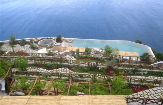 Galleria fotografica






Una foto del Monastero di Santa Rosa, prima della ristrutturazione. Costruito nel 1680, è sospeso a circa 500 metri sul livello del mare di Conca dei Marini, a un passo da Amalfi (Salerno). Prima dell'abbandono è stato gestito dalla famiglia Caterina per 3 generazioni. Nel 2001, l'acquisto dell'ereditiera Bianca Sharma. I lavori di restauro sono durati 11 lunghi anni








La facciata principale del Monastero vista dal terrazzamento della piscina. Le 20 suite, tutte con affaccio su Salerno e sul Cilento fino a Punta Licosa, portano ognuna il nome di un'erba, un fiore o una spezia locale (melissa, viola...). In alta stagione i prezzi oscillano tra i 550 e gli 850 euro a notte per le stanze "standard", fino a 2.950 euro per la Penthouse Suite








La foto non rende bene l'idea delle dimensioni del dirupo. Ma la distanza verticale tra il Monastero e la spiaggia è di 500 metri. La Conca dei Marini porta questo nome perché la stessa "conca" raggiunge una profondità di 800 metri. L'habitat acquatico ideale per diversi pesci da fondale, inclusi totani da 3-4 chili





