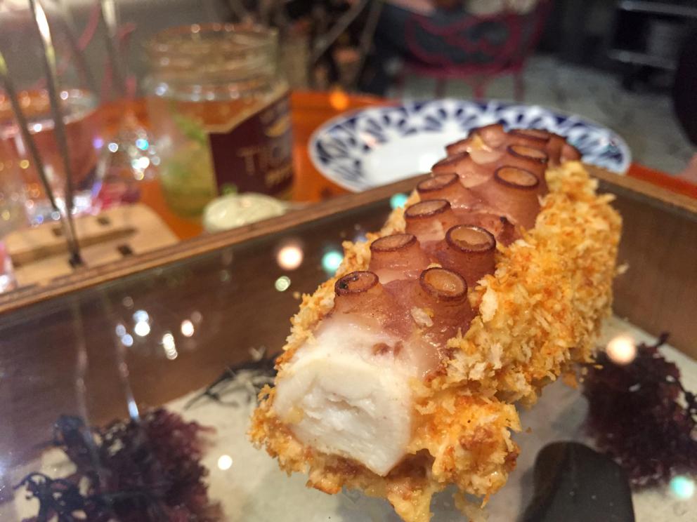 Galleria fotografica






Consommè de garbanzos. Prima che cominci il menu degustazione, viene portata al tavolo una bottiglia di vetro contenente del brodo freddo di ceci (in alto a destra). Ventitrè piatti dopo, alla fine del percorso "salato", verrà versato, in un bicchierino da grappa, del brodo caldo di jamon iberico da una teiera. Sopra ancora, la schiuma del brodo di ceci. Un caldo-freddo speciale (foto @ticketsbar instagram)









Tosta de pollo y anchoa. Primo piatto: toast di pelle di pollo con lisca di acciuga. A lato, una crema di acciughe composta da burro e pasta di acciughe









Olive Gordal. Uno dei simboli della saga Adrià: le olive sono immerse in un liquido d'olio extravergine d'oliva, cannella, buccia di limone e anice stellato. Si tirano su con un cucchiaino forato, si poggiano su una conchiglia di legno a lato e da qui in bocca. Gordal è una varietà dall'Andalusia









Prima preparazione rifinita al tavolo: Polo de almendras









Polo de almendras è uno stecco di gelato al latte di mandorle, spennellato sul posto con olio d'oliva e cosparso con granelle di mandorle, fiori di sambuco e sale. E' servito su un piatto con cubetti di ghiaccio. Dolce(salato) e gelato all'inizio del pasto e non alla fine, uno schema molto Adrià









Coliflor y caviar. Ganache di cavolfiore e caviale russo Schrenkii









Gamba a la sal fría. Gamberi marinati nel tè Lapsang Souchong con zest di bergamotto. Sono serviti su un vassoio con "neve di sale" per ricordare il ghiaccio tipico di un mercato del pesce









Atún con cerezas. Tonno e ciliegia: ventresca di tonno confit in grasso di prosciutto, accompagnata da una ciliegia affumicata (senza nocciolo)









Ceviche de melón cantaloup. Ceviche di melone cantalupo con succo di lime, coriandolo e leche de tigre di kumquat. Servito con kumquat, olio di coriandolo e neve di kumquat. Citrico alla terza









Pizza crujiente. La "pizza" di Tickets: millefoglie di regañà (torta di pane croccante di origini andaluse), stracciatella, bottarga e fichi









Porex de Calix. Marshmallow di dashi ripieno di crema acida e sormontato da caviale di Kalix, uova rosse svedesi di coregone, dalle note dolci ed eleganti









Nigiri de berenjena. Nigiri di melanzana









Cubo de wagyu. Cubo di chips di patata croccante con sopra una tartare di wagyu trattata con olio, sale, senape di Digione, uova e pepe. Una magnifica tapa da circa 2 cm per lato, che ricorda le battute al coltello della tradizione piemontese









Milhojas de atún. Millefoglie di tonno: millefoglie di patata e alga nori. In cima, tartare di tonno leggermente piccante con crema di avocado









Miniairbag de queso. Miniairbag di spuma di formaggio manchego, caviale di nocciola e polvere di buccia di nocciole









Airbaguette de rubia gallega: grissino-baguette vuoto avvolto da fettine di "prosciutto" marinato di rubia gallega, pregiata razza bovina galiziana









Encerradito de buey: involtino di ravioli di avocado con dentro granciporro con maionese di peperoncino chipotle e gelatina di coriandolo. Sotto c'è del pane sardo guttiau, sopra dei semi di chia. Un assaggio cremoso, grasso e vegetale in due bocconi magnifici









Foie y anguila. Foie gras d'anatra di Mitteault ripieno di anguilla avvolta in alga nori









Espardeña con panceta. Cetriolo di mare con la sua pelle fritta e wasabi, sopra una striscia di pancetta di prosciutto Joselito. Forse l'unico punto di domanda






