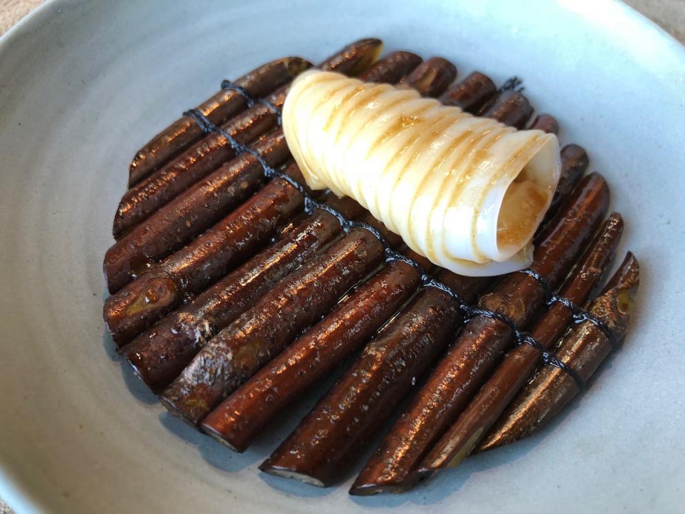 Photogallery






Noma 2.0 is in Christianshavn, the same neighbourhood as the first Noma. They’re 1.5 km apart, a 15 minutes’ walk. This picture shows the distance: to the right, there’s the warehouse of the old location (in Strandgade 93), to the left the smokestacks of Amager Bakke, the futuristic incinerator below which stands the new Noma (in Refshalevej 96)









Weather permitting, you can have a peaceful walk between the previous Noma to today’s Noma 









The new Noma is on an isthmus surrounded by canals. In the future they also want to reclaim some small parts for hydroponic farming









Bucolic scene with incinerator









Bikes left outside Noma. It’s the favourite means of transport among employees and interns









The long path taking you to the restaurant. The fence on the left shows how works are still in progress









On the two sides of the path there are the two new sections of the "Noma village", each with its specialty: grill, hot dishes, snacks, fermentations... In one month’s time, behind the fence we’ll have greenhouses, the test kitchen and the bread making area









To the left, before arriving at the restaurant, the future test kitchen. This will be run by Danish Mette Søberg with Riccardo Canella. "My first challenge?", reveals the latter, for a long time sous chef here, "is to work on the extraction of essential oils" 









The future Test Kitchen









The temporary gangway to the restaurant









Looking from the door to the restaurant, there’s a lake and the smokestacks puffing vapour from the Amager Bakke incinerator. It’s a futuristic project, both in terms of sustainability and architecture. It’s also known as Amager Slope or Copenhill, and its author is starchitect Bjarke Ingels, the same who designed the new Noma. Gradually opened in 2017, it transforms waste into electricity. The goal is to donate electricity to 62500 houses and hot water to 160000. It’s part of an ambitious project to transform Copenhagen into the first city in the world in terms of zero carbon dioxide emissions by 2025. By autumn this year, Amager Slope should open its ski slope, a climbing wall and a hiking track. You’ll be able to slalom on top of the incinerator









The windows from the dining room









Work is still in progress (photo taken on Thursday 22nd February 2018)









Traces of the old building, with barbwire. During WWII, they built bombs here









A view of the dining room at night (photo from Instagram/James Spreadbury)









The entrance to the restaurant









The usual ritual: a welcome from the entire staff, led by Rene Redzepi 









Behind the entrance, there are formaldehyde tanks with creatures from the abyss, shaped as in Damien Hirst’s works. The first image once you’re inside is to reproduce a Scandinavian village









The service kitchen is larger, more spacious and a completely open view from the dining room: "It’s the heart of our Scandinavian village", says Canella. There are 30 cooks working here now. 10 more, compared to the previous Noma









Large skylights above the cooks









There are currently more than 100 people working at Noma, of whom 63 are cooks - 26 employed, and 37 as interns









There’s fire in the kitchen, for the first time









On average, the dining room can host 40 people. "However", complains Redzepi, "there’s always someone who turns up with more people than the ones booked"









While the dining room is set, the outside space still need to be defined









The staff made the dining room decorations. There are no overly expensive designer objects









Dried fish









Seaweeds hanging from the ceiling









Dried octopus heads preserved in salt (with a balloon inside)














Bjarke Ingels and Redzepi’s plan included the wish to recreate a Danish farm









The luminous private dining room









The counter in the dining room. They drew the beams from the canals around the restaurant














The mise en place, bare and strictly without tablecloths









Water jug, candle, flower vase









A warm cloth, to begin with









Australian James Spreadbury, restaurant manager and partner at Noma









Welcome drink: Champagne extra brut Blanc d'Argile from Domaine Vouette et Sorbée









Sea Snail broth. The welcome dish at Noma is, as usual, a hot “soup”









Stefano Ferrano, from Torino, presents the following dish. There’s always a large Italian colony at Noma









Venus clams. Molluscs from Limfjord (Denmark) mixed with decorative clams, typical of Noma. Beside them, shells with blackcurrant oil and “Danish curry”, made with toasted coriander seeds, fennel and fennel seeds









The lid above the following dish. The mussels are not edible









Best of the mussel. Mussels open in a pan with water of fermented barley. «We recreate the mussel», says Canella, «using just the flaps, the best part». The paste is made with scraps from the mussel, cooked in smoked butter









The next dish is conceived and served by Riccardo Canella, the Paduan sous chef who conquered Redzepi, here with dining room intern Feline Hansen









Dried fruits and shrimps. In this case, the heads are not a decoration, but you must suck them –best not eat them because of the bones: they’re filled with a lovely prawn cream. The small crustaceans are still alive when they arrive on a ship straight from the Norwegian fjords









Inside, under the prawn broth skin, there’s fruits and vegetable preserved from the previous summer with raw prawns and gooseberry sauce with blackcurrant oil









How about beverages? There are three options, as usual: wine pairing (6 glasses plus a beer plus sake, 150 euros), juice pairing (juices and extracts, 110 euros) or a choice from the list. They recommend Champagne Chut... Libre from Val'Frison pour Dominique Derain, 50% Pinot Noir, 50% Chardonnay created by a couple who met at the old Noma. Well bodied, it will be a good match throughout the meal









As usual, the wine list starts with Champagne: the cheapest is 1400 crowns (190 euros)









White wines begin with labels from cold climates: first Austria, increasingly popular for its natural wines, then Germany, then all the others









How about Italy? Few names, among the white wines, from North and South









A dozen red/orange wines









Sea star, that is to say Cured trout roe and eggs, the emblem dish of this new era. They recommend moving the teaspoon from the heart to the edges of the tentacles. Aesthetics win over taste









Jellyfish. The jellyfish gel in the middle is in fact a clarified broth of calamari and recalls the texture of jellyfish. "We tried to cook jellyfish in 300 different ways but none was convincing so far". All around, pickled seaweed. The gel is almost tasteless, it serves to clean the palate after the pickles









Rene Redzepi himself presents the content of the first Seafood platter.









French style service with a small plate below for the empty shells









It’s made of two (per two) pieces: queen clam and mahogany clam









The Queen Clam is a very small variety of Norwegian scallop, seasoned with a vegetal reduction made with cucumber and peas miso. The red tip is the coral. "You should eat it using the top shell ", recommends Redzepi









The Mahogany clam is a centennial clam from the North Sea, very popular in Denmark and Iceland. «You can tell the age by the number of rings, like with trees», says Redzepi, «In 2007 they found one that was 450 years old. We’ve had it in the menu for a decade or so». The razor clam shell serves as teaspoon









Inside, there’s obviously not just a bare Mahogany. «We open it when the client arrives», says Canella, «remove the entrails and then slice it so as to preserve its firm texture». It’s seasoned with stir-fried gooseberry, capers of blackcurrants and blackcurrant sprouts preserved in vinegar. The sauce is made with mussel water









A note on the chairs: they’re more minimalistic. They’re no longer covered in sheepskin or leather from other Danish animals, in the style of Noma 1.0. The most significant element is the napkin: if you go to the toilet, they no longer replace it with a new one. There’s the old one, tied to the chair. "This is sustainability", they explain









The second seafood platter. It’s made of Sea cucumber and sour cream in various textures, including «chicharrones» (at 9 o’clock), sea urchins (at 12 and 3) and gigas oyster (at 6)









Sea urchins pressed in fresh cream and pumpkin seeds









Giga Oyster, a huge oyster from the Pacific, quickly steamed and garnished with pickles. Noma only reserved one thousand of these. In the menu until available









The following dish, off the menu, is again from Canella: horse mussel ragout, rare specimen of which 30 arrive at 'Noma each week









They cook the mussel as if it were kidney, in a sort of Bolognese sauce but with ginger. Ginger? "Yes, we’ve decided to include it, as with other spices, after our Mexican experience"









Another Italian presents a dish, Edoardo Fiaschi from Prato, at Noma for 3 years now






