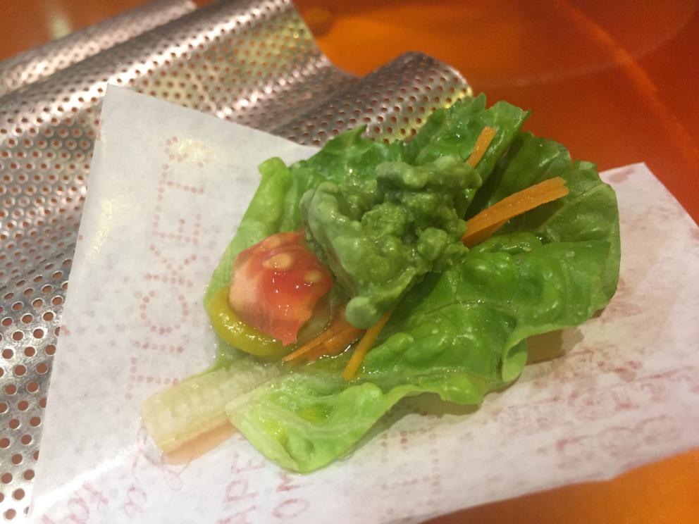 Galleria fotografica






Consommè de garbanzos. Prima che cominci il menu degustazione, viene portata al tavolo una bottiglia di vetro contenente del brodo freddo di ceci (in alto a destra). Ventitrè piatti dopo, alla fine del percorso "salato", verrà versato, in un bicchierino da grappa, del brodo caldo di jamon iberico da una teiera. Sopra ancora, la schiuma del brodo di ceci. Un caldo-freddo speciale (foto @ticketsbar instagram)









Tosta de pollo y anchoa. Primo piatto: toast di pelle di pollo con lisca di acciuga. A lato, una crema di acciughe composta da burro e pasta di acciughe









Olive Gordal. Uno dei simboli della saga Adrià: le olive sono immerse in un liquido d'olio extravergine d'oliva, cannella, buccia di limone e anice stellato. Si tirano su con un cucchiaino forato, si poggiano su una conchiglia di legno a lato e da qui in bocca. Gordal è una varietà dall'Andalusia









Prima preparazione rifinita al tavolo: Polo de almendras









Polo de almendras è uno stecco di gelato al latte di mandorle, spennellato sul posto con olio d'oliva e cosparso con granelle di mandorle, fiori di sambuco e sale. E' servito su un piatto con cubetti di ghiaccio. Dolce(salato) e gelato all'inizio del pasto e non alla fine, uno schema molto Adrià









Coliflor y caviar. Ganache di cavolfiore e caviale russo Schrenkii









Gamba a la sal fría. Gamberi marinati nel tè Lapsang Souchong con zest di bergamotto. Sono serviti su un vassoio con "neve di sale" per ricordare il ghiaccio tipico di un mercato del pesce









Atún con cerezas. Tonno e ciliegia: ventresca di tonno confit in grasso di prosciutto, accompagnata da una ciliegia affumicata (senza nocciolo)









Ceviche de melón cantaloup. Ceviche di melone cantalupo con succo di lime, coriandolo e leche de tigre di kumquat. Servito con kumquat, olio di coriandolo e neve di kumquat. Citrico alla terza









Pizza crujiente. La "pizza" di Tickets: millefoglie di regañà (torta di pane croccante di origini andaluse), stracciatella, bottarga e fichi









Porex de Calix. Marshmallow di dashi ripieno di crema acida e sormontato da caviale di Kalix, uova rosse svedesi di coregone, dalle note dolci ed eleganti









Nigiri de berenjena. Nigiri di melanzana









Cubo de wagyu. Cubo di chips di patata croccante con sopra una tartare di wagyu trattata con olio, sale, senape di Digione, uova e pepe. Una magnifica tapa da circa 2 cm per lato, che ricorda le battute al coltello della tradizione piemontese









Milhojas de atún. Millefoglie di tonno: millefoglie di patata e alga nori. In cima, tartare di tonno leggermente piccante con crema di avocado









Miniairbag de queso. Miniairbag di spuma di formaggio manchego, caviale di nocciola e polvere di buccia di nocciole









Airbaguette de rubia gallega: grissino-baguette vuoto avvolto da fettine di "prosciutto" marinato di rubia gallega, pregiata razza bovina galiziana









Encerradito de buey: involtino di ravioli di avocado con dentro granciporro con maionese di peperoncino chipotle e gelatina di coriandolo. Sotto c'è del pane sardo guttiau, sopra dei semi di chia. Un assaggio cremoso, grasso e vegetale in due bocconi magnifici









Foie y anguila. Foie gras d'anatra di Mitteault ripieno di anguilla avvolta in alga nori









Espardeña con panceta. Cetriolo di mare con la sua pelle fritta e wasabi, sopra una striscia di pancetta di prosciutto Joselito. Forse l'unico punto di domanda









Pulpo crujiente. Octopus tenero in panko (pangrattato giapponese piccante) croccante, accompagnato da cetrioli baby pickled






