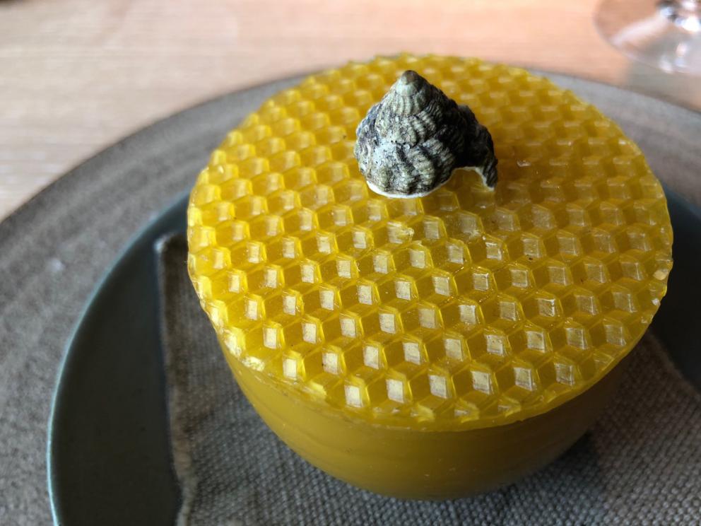 Photogallery






Noma 2.0 is in Christianshavn, the same neighbourhood as the first Noma. They’re 1.5 km apart, a 15 minutes’ walk. This picture shows the distance: to the right, there’s the warehouse of the old location (in Strandgade 93), to the left the smokestacks of Amager Bakke, the futuristic incinerator below which stands the new Noma (in Refshalevej 96)









Weather permitting, you can have a peaceful walk between the previous Noma to today’s Noma 









The new Noma is on an isthmus surrounded by canals. In the future they also want to reclaim some small parts for hydroponic farming









Bucolic scene with incinerator









Bikes left outside Noma. It’s the favourite means of transport among employees and interns









The long path taking you to the restaurant. The fence on the left shows how works are still in progress









On the two sides of the path there are the two new sections of the "Noma village", each with its specialty: grill, hot dishes, snacks, fermentations... In one month’s time, behind the fence we’ll have greenhouses, the test kitchen and the bread making area









To the left, before arriving at the restaurant, the future test kitchen. This will be run by Danish Mette Søberg with Riccardo Canella. "My first challenge?", reveals the latter, for a long time sous chef here, "is to work on the extraction of essential oils" 









The future Test Kitchen









The temporary gangway to the restaurant









Looking from the door to the restaurant, there’s a lake and the smokestacks puffing vapour from the Amager Bakke incinerator. It’s a futuristic project, both in terms of sustainability and architecture. It’s also known as Amager Slope or Copenhill, and its author is starchitect Bjarke Ingels, the same who designed the new Noma. Gradually opened in 2017, it transforms waste into electricity. The goal is to donate electricity to 62500 houses and hot water to 160000. It’s part of an ambitious project to transform Copenhagen into the first city in the world in terms of zero carbon dioxide emissions by 2025. By autumn this year, Amager Slope should open its ski slope, a climbing wall and a hiking track. You’ll be able to slalom on top of the incinerator









The windows from the dining room









Work is still in progress (photo taken on Thursday 22nd February 2018)









Traces of the old building, with barbwire. During WWII, they built bombs here









A view of the dining room at night (photo from Instagram/James Spreadbury)









The entrance to the restaurant









The usual ritual: a welcome from the entire staff, led by Rene Redzepi 









Behind the entrance, there are formaldehyde tanks with creatures from the abyss, shaped as in Damien Hirst’s works. The first image once you’re inside is to reproduce a Scandinavian village









The service kitchen is larger, more spacious and a completely open view from the dining room: "It’s the heart of our Scandinavian village", says Canella. There are 30 cooks working here now. 10 more, compared to the previous Noma









Large skylights above the cooks









There are currently more than 100 people working at Noma, of whom 63 are cooks - 26 employed, and 37 as interns









There’s fire in the kitchen, for the first time









On average, the dining room can host 40 people. "However", complains Redzepi, "there’s always someone who turns up with more people than the ones booked"









While the dining room is set, the outside space still need to be defined









The staff made the dining room decorations. There are no overly expensive designer objects









Dried fish









Seaweeds hanging from the ceiling









Dried octopus heads preserved in salt (with a balloon inside)














Bjarke Ingels and Redzepi’s plan included the wish to recreate a Danish farm









The luminous private dining room









The counter in the dining room. They drew the beams from the canals around the restaurant














The mise en place, bare and strictly without tablecloths









Water jug, candle, flower vase









A warm cloth, to begin with









Australian James Spreadbury, restaurant manager and partner at Noma









Welcome drink: Champagne extra brut Blanc d'Argile from Domaine Vouette et Sorbée









Sea Snail broth. The welcome dish at Noma is, as usual, a hot “soup”









Stefano Ferrano, from Torino, presents the following dish. There’s always a large Italian colony at Noma









Venus clams. Molluscs from Limfjord (Denmark) mixed with decorative clams, typical of Noma. Beside them, shells with blackcurrant oil and “Danish curry”, made with toasted coriander seeds, fennel and fennel seeds









The lid above the following dish. The mussels are not edible









Best of the mussel. Mussels open in a pan with water of fermented barley. «We recreate the mussel», says Canella, «using just the flaps, the best part». The paste is made with scraps from the mussel, cooked in smoked butter









The next dish is conceived and served by Riccardo Canella, the Paduan sous chef who conquered Redzepi, here with dining room intern Feline Hansen









Dried fruits and shrimps. In this case, the heads are not a decoration, but you must suck them –best not eat them because of the bones: they’re filled with a lovely prawn cream. The small crustaceans are still alive when they arrive on a ship straight from the Norwegian fjords









Inside, under the prawn broth skin, there’s fruits and vegetable preserved from the previous summer with raw prawns and gooseberry sauce with blackcurrant oil









How about beverages? There are three options, as usual: wine pairing (6 glasses plus a beer plus sake, 150 euros), juice pairing (juices and extracts, 110 euros) or a choice from the list. They recommend Champagne Chut... Libre from Val'Frison pour Dominique Derain, 50% Pinot Noir, 50% Chardonnay created by a couple who met at the old Noma. Well bodied, it will be a good match throughout the meal









As usual, the wine list starts with Champagne: the cheapest is 1400 crowns (190 euros)









White wines begin with labels from cold climates: first Austria, increasingly popular for its natural wines, then Germany, then all the others









How about Italy? Few names, among the white wines, from North and South









A dozen red/orange wines









Sea star, that is to say Cured trout roe and eggs, the emblem dish of this new era. They recommend moving the teaspoon from the heart to the edges of the tentacles. Aesthetics win over taste









Jellyfish. The jellyfish gel in the middle is in fact a clarified broth of calamari and recalls the texture of jellyfish. "We tried to cook jellyfish in 300 different ways but none was convincing so far". All around, pickled seaweed. The gel is almost tasteless, it serves to clean the palate after the pickles









Rene Redzepi himself presents the content of the first Seafood platter.









French style service with a small plate below for the empty shells









It’s made of two (per two) pieces: queen clam and mahogany clam









The Queen Clam is a very small variety of Norwegian scallop, seasoned with a vegetal reduction made with cucumber and peas miso. The red tip is the coral. "You should eat it using the top shell ", recommends Redzepi









The Mahogany clam is a centennial clam from the North Sea, very popular in Denmark and Iceland. «You can tell the age by the number of rings, like with trees», says Redzepi, «In 2007 they found one that was 450 years old. We’ve had it in the menu for a decade or so». The razor clam shell serves as teaspoon









Inside, there’s obviously not just a bare Mahogany. «We open it when the client arrives», says Canella, «remove the entrails and then slice it so as to preserve its firm texture». It’s seasoned with stir-fried gooseberry, capers of blackcurrants and blackcurrant sprouts preserved in vinegar. The sauce is made with mussel water









A note on the chairs: they’re more minimalistic. They’re no longer covered in sheepskin or leather from other Danish animals, in the style of Noma 1.0. The most significant element is the napkin: if you go to the toilet, they no longer replace it with a new one. There’s the old one, tied to the chair. "This is sustainability", they explain









The second seafood platter. It’s made of Sea cucumber and sour cream in various textures, including «chicharrones» (at 9 o’clock), sea urchins (at 12 and 3) and gigas oyster (at 6)









Sea urchins pressed in fresh cream and pumpkin seeds









Giga Oyster, a huge oyster from the Pacific, quickly steamed and garnished with pickles. Noma only reserved one thousand of these. In the menu until available









The following dish, off the menu, is again from Canella: horse mussel ragout, rare specimen of which 30 arrive at 'Noma each week









They cook the mussel as if it were kidney, in a sort of Bolognese sauce but with ginger. Ginger? "Yes, we’ve decided to include it, as with other spices, after our Mexican experience"









Another Italian presents a dish, Edoardo Fiaschi from Prato, at Noma for 3 years now









Squid in seaweed butter. An almost neglected Danish squid lightly seared in fermented koji oil, rolled and seasoned with seaweed butter and served on sticks of blackcurrant that widen its aromas. Formidable and beautiful






