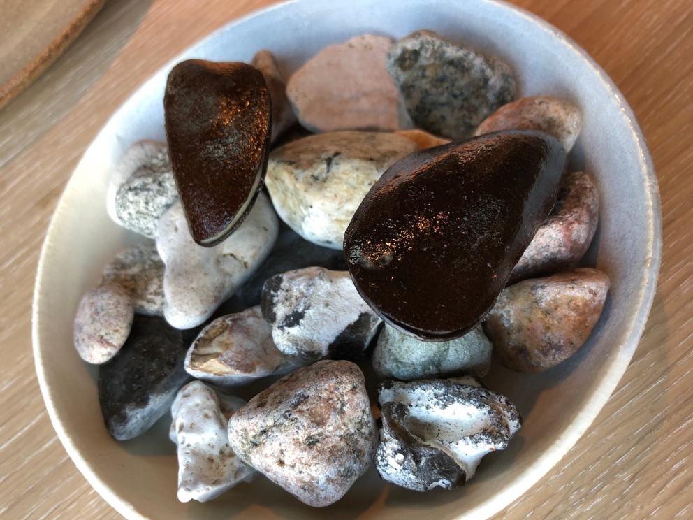 Photogallery






Noma 2.0 is in Christianshavn, the same neighbourhood as the first Noma. They’re 1.5 km apart, a 15 minutes’ walk. This picture shows the distance: to the right, there’s the warehouse of the old location (in Strandgade 93), to the left the smokestacks of Amager Bakke, the futuristic incinerator below which stands the new Noma (in Refshalevej 96)









Weather permitting, you can have a peaceful walk between the previous Noma to today’s Noma 









The new Noma is on an isthmus surrounded by canals. In the future they also want to reclaim some small parts for hydroponic farming









Bucolic scene with incinerator









Bikes left outside Noma. It’s the favourite means of transport among employees and interns









The long path taking you to the restaurant. The fence on the left shows how works are still in progress









On the two sides of the path there are the two new sections of the "Noma village", each with its specialty: grill, hot dishes, snacks, fermentations... In one month’s time, behind the fence we’ll have greenhouses, the test kitchen and the bread making area









To the left, before arriving at the restaurant, the future test kitchen. This will be run by Danish Mette Søberg with Riccardo Canella. "My first challenge?", reveals the latter, for a long time sous chef here, "is to work on the extraction of essential oils" 









The future Test Kitchen









The temporary gangway to the restaurant









Looking from the door to the restaurant, there’s a lake and the smokestacks puffing vapour from the Amager Bakke incinerator. It’s a futuristic project, both in terms of sustainability and architecture. It’s also known as Amager Slope or Copenhill, and its author is starchitect Bjarke Ingels, the same who designed the new Noma. Gradually opened in 2017, it transforms waste into electricity. The goal is to donate electricity to 62500 houses and hot water to 160000. It’s part of an ambitious project to transform Copenhagen into the first city in the world in terms of zero carbon dioxide emissions by 2025. By autumn this year, Amager Slope should open its ski slope, a climbing wall and a hiking track. You’ll be able to slalom on top of the incinerator









The windows from the dining room









Work is still in progress (photo taken on Thursday 22nd February 2018)









Traces of the old building, with barbwire. During WWII, they built bombs here









A view of the dining room at night (photo from Instagram/James Spreadbury)









The entrance to the restaurant









The usual ritual: a welcome from the entire staff, led by Rene Redzepi 









Behind the entrance, there are formaldehyde tanks with creatures from the abyss, shaped as in Damien Hirst’s works. The first image once you’re inside is to reproduce a Scandinavian village









The service kitchen is larger, more spacious and a completely open view from the dining room: "It’s the heart of our Scandinavian village", says Canella. There are 30 cooks working here now. 10 more, compared to the previous Noma









Large skylights above the cooks









There are currently more than 100 people working at Noma, of whom 63 are cooks - 26 employed, and 37 as interns









There’s fire in the kitchen, for the first time









On average, the dining room can host 40 people. "However", complains Redzepi, "there’s always someone who turns up with more people than the ones booked"









While the dining room is set, the outside space still need to be defined









The staff made the dining room decorations. There are no overly expensive designer objects









Dried fish









Seaweeds hanging from the ceiling









Dried octopus heads preserved in salt (with a balloon inside)














Bjarke Ingels and Redzepi’s plan included the wish to recreate a Danish farm









The luminous private dining room









The counter in the dining room. They drew the beams from the canals around the restaurant














The mise en place, bare and strictly without tablecloths









Water jug, candle, flower vase









A warm cloth, to begin with









Australian James Spreadbury, restaurant manager and partner at Noma









Welcome drink: Champagne extra brut Blanc d'Argile from Domaine Vouette et Sorbée









Sea Snail broth. The welcome dish at Noma is, as usual, a hot “soup”









Stefano Ferrano, from Torino, presents the following dish. There’s always a large Italian colony at Noma









Venus clams. Molluscs from Limfjord (Denmark) mixed with decorative clams, typical of Noma. Beside them, shells with blackcurrant oil and “Danish curry”, made with toasted coriander seeds, fennel and fennel seeds









The lid above the following dish. The mussels are not edible









Best of the mussel. Mussels open in a pan with water of fermented barley. «We recreate the mussel», says Canella, «using just the flaps, the best part». The paste is made with scraps from the mussel, cooked in smoked butter









The next dish is conceived and served by Riccardo Canella, the Paduan sous chef who conquered Redzepi, here with dining room intern Feline Hansen









Dried fruits and shrimps. In this case, the heads are not a decoration, but you must suck them –best not eat them because of the bones: they’re filled with a lovely prawn cream. The small crustaceans are still alive when they arrive on a ship straight from the Norwegian fjords









Inside, under the prawn broth skin, there’s fruits and vegetable preserved from the previous summer with raw prawns and gooseberry sauce with blackcurrant oil









How about beverages? There are three options, as usual: wine pairing (6 glasses plus a beer plus sake, 150 euros), juice pairing (juices and extracts, 110 euros) or a choice from the list. They recommend Champagne Chut... Libre from Val'Frison pour Dominique Derain, 50% Pinot Noir, 50% Chardonnay created by a couple who met at the old Noma. Well bodied, it will be a good match throughout the meal









As usual, the wine list starts with Champagne: the cheapest is 1400 crowns (190 euros)









White wines begin with labels from cold climates: first Austria, increasingly popular for its natural wines, then Germany, then all the others









How about Italy? Few names, among the white wines, from North and South









A dozen red/orange wines









Sea star, that is to say Cured trout roe and eggs, the emblem dish of this new era. They recommend moving the teaspoon from the heart to the edges of the tentacles. Aesthetics win over taste









Jellyfish. The jellyfish gel in the middle is in fact a clarified broth of calamari and recalls the texture of jellyfish. "We tried to cook jellyfish in 300 different ways but none was convincing so far". All around, pickled seaweed. The gel is almost tasteless, it serves to clean the palate after the pickles









Rene Redzepi himself presents the content of the first Seafood platter.









French style service with a small plate below for the empty shells









It’s made of two (per two) pieces: queen clam and mahogany clam









The Queen Clam is a very small variety of Norwegian scallop, seasoned with a vegetal reduction made with cucumber and peas miso. The red tip is the coral. "You should eat it using the top shell ", recommends Redzepi









The Mahogany clam is a centennial clam from the North Sea, very popular in Denmark and Iceland. «You can tell the age by the number of rings, like with trees», says Redzepi, «In 2007 they found one that was 450 years old. We’ve had it in the menu for a decade or so». The razor clam shell serves as teaspoon









Inside, there’s obviously not just a bare Mahogany. «We open it when the client arrives», says Canella, «remove the entrails and then slice it so as to preserve its firm texture». It’s seasoned with stir-fried gooseberry, capers of blackcurrants and blackcurrant sprouts preserved in vinegar. The sauce is made with mussel water









A note on the chairs: they’re more minimalistic. They’re no longer covered in sheepskin or leather from other Danish animals, in the style of Noma 1.0. The most significant element is the napkin: if you go to the toilet, they no longer replace it with a new one. There’s the old one, tied to the chair. "This is sustainability", they explain









The second seafood platter. It’s made of Sea cucumber and sour cream in various textures, including «chicharrones» (at 9 o’clock), sea urchins (at 12 and 3) and gigas oyster (at 6)









Sea urchins pressed in fresh cream and pumpkin seeds









Giga Oyster, a huge oyster from the Pacific, quickly steamed and garnished with pickles. Noma only reserved one thousand of these. In the menu until available









The following dish, off the menu, is again from Canella: horse mussel ragout, rare specimen of which 30 arrive at 'Noma each week









They cook the mussel as if it were kidney, in a sort of Bolognese sauce but with ginger. Ginger? "Yes, we’ve decided to include it, as with other spices, after our Mexican experience"









Another Italian presents a dish, Edoardo Fiaschi from Prato, at Noma for 3 years now









Squid in seaweed butter. An almost neglected Danish squid lightly seared in fermented koji oil, rolled and seasoned with seaweed butter and served on sticks of blackcurrant that widen its aromas. Formidable and beautiful









The following dish is inside a nice bee wax container. It’s made with balloons covered multiple times in bee wax. «We spent weeks making them. We’ve made thousands». They’re disposable...









Sea snail and roses. They recommend to: "Eat it keeping the bee wax on your hands "









Sea snail. Another small nibble from the top part of the sea snail, lightly warmed up in water and served on a reduction of lemon thyme









A sea snail toothpick, initially carved by Redzepi himself









Head of the cod, (right), the real main course at Noma









Another rather laborious recipe. «It takes half an hour just to separate the head. We remove the skin, the collagen, we cut mandibles, tongue, cheek and the part behind. We rinse it in water, spices, koji and cook it in the yakitori with a glaze of mushrooms and spiced fennel broth»









You can garnish the cod as you choose, with a paste of ants (top right corner), a slightly spicy emulsion of koji oil, water and horseradish sauce (left) and Danish curry (bottom)









On the side of the cod, there’s also wild garlic seasoned with smoked butter and roasted yeast. Intense flavour









Cod bones after the tasting









An interlocutory snack made of cod cheek









Pickled vegetables and arctic herbs. The only vegetable dish in the menu, marks the passage from savoury to sweet dishes. Between June and August 2018 the menu at Noma will be 100% vegetarian









Preparation time: half an hour! A challenge for the person making it






