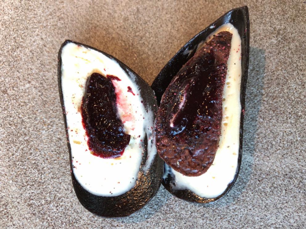 Photogallery






Noma 2.0 is in Christianshavn, the same neighbourhood as the first Noma. They’re 1.5 km apart, a 15 minutes’ walk. This picture shows the distance: to the right, there’s the warehouse of the old location (in Strandgade 93), to the left the smokestacks of Amager Bakke, the futuristic incinerator below which stands the new Noma (in Refshalevej 96)









Weather permitting, you can have a peaceful walk between the previous Noma to today’s Noma 









The new Noma is on an isthmus surrounded by canals. In the future they also want to reclaim some small parts for hydroponic farming









Bucolic scene with incinerator









Bikes left outside Noma. It’s the favourite means of transport among employees and interns









The long path taking you to the restaurant. The fence on the left shows how works are still in progress









On the two sides of the path there are the two new sections of the "Noma village", each with its specialty: grill, hot dishes, snacks, fermentations... In one month’s time, behind the fence we’ll have greenhouses, the test kitchen and the bread making area









To the left, before arriving at the restaurant, the future test kitchen. This will be run by Danish Mette Søberg with Riccardo Canella. "My first challenge?", reveals the latter, for a long time sous chef here, "is to work on the extraction of essential oils" 









The future Test Kitchen









The temporary gangway to the restaurant









Looking from the door to the restaurant, there’s a lake and the smokestacks puffing vapour from the Amager Bakke incinerator. It’s a futuristic project, both in terms of sustainability and architecture. It’s also known as Amager Slope or Copenhill, and its author is starchitect Bjarke Ingels, the same who designed the new Noma. Gradually opened in 2017, it transforms waste into electricity. The goal is to donate electricity to 62500 houses and hot water to 160000. It’s part of an ambitious project to transform Copenhagen into the first city in the world in terms of zero carbon dioxide emissions by 2025. By autumn this year, Amager Slope should open its ski slope, a climbing wall and a hiking track. You’ll be able to slalom on top of the incinerator









The windows from the dining room









Work is still in progress (photo taken on Thursday 22nd February 2018)









Traces of the old building, with barbwire. During WWII, they built bombs here









A view of the dining room at night (photo from Instagram/James Spreadbury)









The entrance to the restaurant









The usual ritual: a welcome from the entire staff, led by Rene Redzepi 









Behind the entrance, there are formaldehyde tanks with creatures from the abyss, shaped as in Damien Hirst’s works. The first image once you’re inside is to reproduce a Scandinavian village









The service kitchen is larger, more spacious and a completely open view from the dining room: "It’s the heart of our Scandinavian village", says Canella. There are 30 cooks working here now. 10 more, compared to the previous Noma









Large skylights above the cooks









There are currently more than 100 people working at Noma, of whom 63 are cooks - 26 employed, and 37 as interns









There’s fire in the kitchen, for the first time









On average, the dining room can host 40 people. "However", complains Redzepi, "there’s always someone who turns up with more people than the ones booked"









While the dining room is set, the outside space still need to be defined









The staff made the dining room decorations. There are no overly expensive designer objects









Dried fish









Seaweeds hanging from the ceiling









Dried octopus heads preserved in salt (with a balloon inside)














Bjarke Ingels and Redzepi’s plan included the wish to recreate a Danish farm









The luminous private dining room









The counter in the dining room. They drew the beams from the canals around the restaurant














The mise en place, bare and strictly without tablecloths









Water jug, candle, flower vase









A warm cloth, to begin with









Australian James Spreadbury, restaurant manager and partner at Noma









Welcome drink: Champagne extra brut Blanc d'Argile from Domaine Vouette et Sorbée









Sea Snail broth. The welcome dish at Noma is, as usual, a hot “soup”









Stefano Ferrano, from Torino, presents the following dish. There’s always a large Italian colony at Noma









Venus clams. Molluscs from Limfjord (Denmark) mixed with decorative clams, typical of Noma. Beside them, shells with blackcurrant oil and “Danish curry”, made with toasted coriander seeds, fennel and fennel seeds









The lid above the following dish. The mussels are not edible









Best of the mussel. Mussels open in a pan with water of fermented barley. «We recreate the mussel», says Canella, «using just the flaps, the best part». The paste is made with scraps from the mussel, cooked in smoked butter









The next dish is conceived and served by Riccardo Canella, the Paduan sous chef who conquered Redzepi, here with dining room intern Feline Hansen









Dried fruits and shrimps. In this case, the heads are not a decoration, but you must suck them –best not eat them because of the bones: they’re filled with a lovely prawn cream. The small crustaceans are still alive when they arrive on a ship straight from the Norwegian fjords









Inside, under the prawn broth skin, there’s fruits and vegetable preserved from the previous summer with raw prawns and gooseberry sauce with blackcurrant oil









How about beverages? There are three options, as usual: wine pairing (6 glasses plus a beer plus sake, 150 euros), juice pairing (juices and extracts, 110 euros) or a choice from the list. They recommend Champagne Chut... Libre from Val'Frison pour Dominique Derain, 50% Pinot Noir, 50% Chardonnay created by a couple who met at the old Noma. Well bodied, it will be a good match throughout the meal









As usual, the wine list starts with Champagne: the cheapest is 1400 crowns (190 euros)









White wines begin with labels from cold climates: first Austria, increasingly popular for its natural wines, then Germany, then all the others









How about Italy? Few names, among the white wines, from North and South









A dozen red/orange wines









Sea star, that is to say Cured trout roe and eggs, the emblem dish of this new era. They recommend moving the teaspoon from the heart to the edges of the tentacles. Aesthetics win over taste









Jellyfish. The jellyfish gel in the middle is in fact a clarified broth of calamari and recalls the texture of jellyfish. "We tried to cook jellyfish in 300 different ways but none was convincing so far". All around, pickled seaweed. The gel is almost tasteless, it serves to clean the palate after the pickles









Rene Redzepi himself presents the content of the first Seafood platter.









French style service with a small plate below for the empty shells









It’s made of two (per two) pieces: queen clam and mahogany clam









The Queen Clam is a very small variety of Norwegian scallop, seasoned with a vegetal reduction made with cucumber and peas miso. The red tip is the coral. "You should eat it using the top shell ", recommends Redzepi









The Mahogany clam is a centennial clam from the North Sea, very popular in Denmark and Iceland. «You can tell the age by the number of rings, like with trees», says Redzepi, «In 2007 they found one that was 450 years old. We’ve had it in the menu for a decade or so». The razor clam shell serves as teaspoon









Inside, there’s obviously not just a bare Mahogany. «We open it when the client arrives», says Canella, «remove the entrails and then slice it so as to preserve its firm texture». It’s seasoned with stir-fried gooseberry, capers of blackcurrants and blackcurrant sprouts preserved in vinegar. The sauce is made with mussel water









A note on the chairs: they’re more minimalistic. They’re no longer covered in sheepskin or leather from other Danish animals, in the style of Noma 1.0. The most significant element is the napkin: if you go to the toilet, they no longer replace it with a new one. There’s the old one, tied to the chair. "This is sustainability", they explain









The second seafood platter. It’s made of Sea cucumber and sour cream in various textures, including «chicharrones» (at 9 o’clock), sea urchins (at 12 and 3) and gigas oyster (at 6)









Sea urchins pressed in fresh cream and pumpkin seeds









Giga Oyster, a huge oyster from the Pacific, quickly steamed and garnished with pickles. Noma only reserved one thousand of these. In the menu until available









The following dish, off the menu, is again from Canella: horse mussel ragout, rare specimen of which 30 arrive at 'Noma each week









They cook the mussel as if it were kidney, in a sort of Bolognese sauce but with ginger. Ginger? "Yes, we’ve decided to include it, as with other spices, after our Mexican experience"









Another Italian presents a dish, Edoardo Fiaschi from Prato, at Noma for 3 years now









Squid in seaweed butter. An almost neglected Danish squid lightly seared in fermented koji oil, rolled and seasoned with seaweed butter and served on sticks of blackcurrant that widen its aromas. Formidable and beautiful









The following dish is inside a nice bee wax container. It’s made with balloons covered multiple times in bee wax. «We spent weeks making them. We’ve made thousands». They’re disposable...









Sea snail and roses. They recommend to: "Eat it keeping the bee wax on your hands "









Sea snail. Another small nibble from the top part of the sea snail, lightly warmed up in water and served on a reduction of lemon thyme









A sea snail toothpick, initially carved by Redzepi himself









Head of the cod, (right), the real main course at Noma









Another rather laborious recipe. «It takes half an hour just to separate the head. We remove the skin, the collagen, we cut mandibles, tongue, cheek and the part behind. We rinse it in water, spices, koji and cook it in the yakitori with a glaze of mushrooms and spiced fennel broth»









You can garnish the cod as you choose, with a paste of ants (top right corner), a slightly spicy emulsion of koji oil, water and horseradish sauce (left) and Danish curry (bottom)









On the side of the cod, there’s also wild garlic seasoned with smoked butter and roasted yeast. Intense flavour









Cod bones after the tasting









An interlocutory snack made of cod cheek









Pickled vegetables and arctic herbs. The only vegetable dish in the menu, marks the passage from savoury to sweet dishes. Between June and August 2018 the menu at Noma will be 100% vegetarian









Preparation time: half an hour! A challenge for the person making it









Mussels appear once again, a classic emblem






