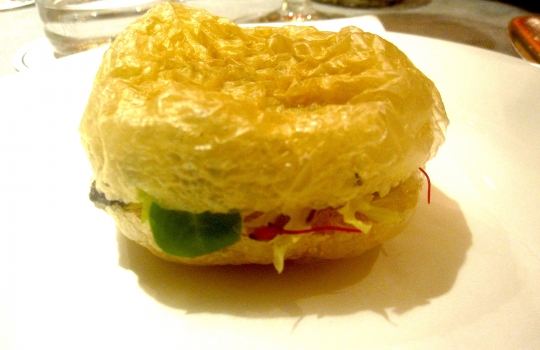 Galleria fotograficaSpugne di pane aromatizzate
Dopo il consueto pre-appetizer delle verdure disidratate (primo contenitore), arrivano le spugne, seconda parentesi colorata che rallegra il pasto dall&rsquo;inizio. In questo caso sono aromatizzate agli spinaci e uova di salmone; alla cipolla cotta al forno con terrina di vitello e alla curcuma con lardo. &laquo;Ma le combinazioni possono essere infinite&raquo;, spiega Matteo Baronetto, braccio destro di Carlo Cracco, &laquo;si possono utilizzare anche in pasticceria al cocco, ai lamponi&hellip; La tecnica &egrave; mutuata da Ferran Adri&agrave;. Abbiamo cercato di personalizzarla nel gusto. A me ricordano molto i canap&egrave; della tradizione piemontese. Senza maionese naturalmente&raquo;. Vivacit&agrave; cromatica ulteriormente ravvivata da un terzo contenitore di foglie di shiso e fiori di zucchina in tempura con riso venere e riso ai piselli fritto (che non vedete perch&eacute;, ahinoi, la foto &egrave; venuta male)Lamponi e sambuco
Nella girandola di appetizer spiccano questi piccoli lamponi farciti con infusione di sambuco serviti sul ghiaccio. &laquo;I suoi fiori in questi giorni li senti anche a Milano, passeggiando al parco. Un odore forte e piacevole. Stiamo lavorando allo stesso concetto anche con le fragole, i mirtilli, il ribes o i gelsi. Un'idea che interpreta quella tradizione sudamericana che ribalta l'ordine delle pietanze, con la frutta all'inizio del percorso, un po' come gi&agrave; succede con la nostra insalata russa caramellata. Sposa nota fruttate e speziate. Ma al posto della frutta potrebbe starci benissimo un'oliva, perch&eacute; no?&raquo;