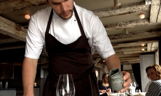 Galleria fotografica






In cammino verso il Noma. Il ristorante è al piano terra del palazzone più a sinistra. Per arrivarci dalla popolare insenatura di Nyhavn (il punto da cui è scattata la foto), occorre fare un bel giro. Ma si notano i lavori per la costruzione di un ponte. Che condurrà dritto all'insegna








Altra prospettiva sul Noma da Nyhavn. Il ristorante galleggia sulla Christianshavn, una delle tante isole artificiali che compongono Copenhagen








Di là del fiume, sulla lunga via che conduce allo spiazzo del Noma








Uno scenario molto tranquillo, di case pastello. Il silenzio è perché vanno tutti in bici













Al massimo si sente rombare qualche scafo








Il vascello davanti al Noma. Oltre a quella danese, sventolano le bandiere di Isole Far Oer e Groenlandia: le loro ambasciate sono nello stesso palazzo del ristorante. Coerenza nordica








Il retro del ristorante. L'80% delle 80 persone che lavorano al Noma viene a lavorare in bici, chef incluso








Dietro al ristorante, un'iscrizione ricorda i passeggeri scomparsi a bordo della danese Hans Hedtoft. Il transatlantico si scontrò il 30 gennaio 1959 contrò un iceberg in Groenlandia. Fu ritrovata solo una cintura di sicurezza
 








L'ingresso del ristorante, al civico 93 di Strandgade








La vista, ingresso alle spalle








Tra l'ingresso e la cucina a vista, spicca un corner di decoro simil-giapponese. A sinistra s'intravede Noma, time and place in Nordic Cuisine, edizioni Phaidon, un testo fondamentale per approfondire tutti i rivoli del Redzepi-mondo. La versione italiana si ordina qui








Una pianta di piccoli agrumi orla la cucina a vista








La porta d'ingresso vista dalla cucina








Le sedie, molto comode, sono anni Sessanta con schienali foderati di pelle di pecora, alcune più morbide di altre








I tavoli sono ampi e senza tovaglie. Attorno prevale il grigio e i colori rustici, sulle travi in legno del soffitto ma anche sulle divise dei ragazzi di sala








La finestra accanto al nostro tavolo








E' lo chef Rene Redzepi a introdurci al pasto: in un vaso di fiori danesi, l'unico pendaglio commestibile è una sorta di carta musica croccante (flatbread) di farina di malto all'aroma di ginepro. Nel piattino in basso, una deliziosa crème fraîche acida per intingerlo








Il flatbread è quello che svetta. "Ma se ci tenete, provate a mangiare anche i fiori", scherza Redzepi. Il cuoco scompare nelle segrete del Noma. Lo ritroveremo solo alla fine del pasto








Tutti i 14 appetizer si mangeranno con le mani. Unica posata, il coltello per tirar su e leccare la crème fraîche da sola (da fare quando tutti gli altri clienti son distratti, però)








Moss and Cep: Muschio di renna con polvere di funghi porcini. E' il corpo bianco, molto saporito ed evanescente, da intingere anch'esso nella crème fraîche
 








Crispy pork skin and black currant: Pelle di maiale croccante e ribes nero, lo strato più esterno. Aspro e croccante








Il ribes nero non ci lascerà prima di molto tempo








Blue mussels and celery: cozze e sedano. Solo due sono quelle buone








La parte inferiore del guscio è commestibile (ancora farina di malto)








Il quinto appetizer è nascosto in una deliziosa scatola di biscotti in latta della tradizione danese (chi non ricorda i Danish butter cookies?)








Cinque tondini, ma solo due "interessanti"








Si chiamano Cheese cookies, rocket and stems, letteralmente Biscotti al formaggio, ruchetta e gambi di erbe aromatiche, un felice snack potenzialmente riproducibile nei nord e nei sud del mondo








Appetizer #6: Potato and duck liver, Patate e fegato d'anatra: le patate croccanti sono in due strati e a mo' di sandwich racchiudono la mousse di fegato. La spolverata è di funghi trombette dei morti, disidratati e polverizzati, una tecnica che troveremo frequentemente








Dried carrot and sorrel, Carote grigliate a fuoco lento per 14 ore, disidratate e servite su polvere di fieno. Si intingono nell'emulsione di acetosella accanto. Un grande piatto perché di inattesa, energica acidità








Ottava entrée: Caramelized milk and cod liver, Biscotto di latte caramellato e fegato di merluzzo, quest'ultimo ghiacciato e pulito. Il secondo dona un aroma molto strong, che domina sul biscotto croccante. Per palati muscolari








Le uova dentro l'uovo








Pickled and smoked quails eggs, Uova di quaglia sbollentate, marinate e affumicate, un classico del Noma. Il tuorlo è completamente liquido








Col Veal fibres and söl, Filamenti di vitello e söl, decimo appetizer, entra in gioco per la prima volta un'alga di mare. E' il söl, appunto, dulse in inglese, Palmaria palmata nella tassonomia scientifica, un'alga rossa incastrata nei filamenti di vitello precedentemente tagliati sottili e poi fritti. Curioso l'impiatto a nido di ingredienti che alla fine incastrano terra e mare








Herb Toast and smoked cod roe, Toast alle erbe e uova di merluzzo affumicato, un'altra grandiosa tapa nordica da far su in due bocconi. Se non ricordiamo male, lo strato superiore è brodo di fegato d'anatra disidratato








Radish, soil and grass, Rapanello, "suolo" ed erba, un altro grande classico del Noma, un paesaggio commestibile di chiara genesi basca-adrianesca, molto replicato negli anni. Carote baby e rapanelli sono interrati in un "suolo" che è una crema di farina di malto con nocciole disidratate. Sotto ancora, uno yogurt di erbe. Finite le verdure, abbiamo chiesto dei cucchiaini per ripulire il suolo








Una foto (di spreadbutter) chiarisce meglio il contenuto del vasetto








Æbleskiver e muikku, penultimo appetizer, di concezione piuttosto recente. Un'antica tradizione dolce danese (Æbleskiver significa "piccoli pezzi di mela" ma la mela qui non c'è) è presentata in versione salata. Code e teste dei muikku, sorta di aringhe baby, sono infilzate in due bigné dall'impasto molto morbido con del ripieno di cetriolo marinato, ben riconoscibile al palato. L'aspetto dispone il cliente alla sfida ma la sua bizzarria visiva si scioglie presto in due bocconi morbidi, eleganti e deliziosi








Ultimo di 14 appetizer: Sorrel leaf and cricket paste, Foglia di acetosella (leggermente piccante) con pasta di grillo. Sì, proprio l'insetto dei prati, qui in consistenza di crema, inserita nel gambo dell'acetosella. Mettendo a fermentare grilli e orzo fermentato, Redzepi ha ottenuto una sorta di garum molto interessante, simile alla soia. Completa il piatto in foto, una granita di nasturzio ghiacciato








E il vino? Non producendo la Danimarca nettari di rilievo, è forse il capitolo meno allettante del Noma. La carta è un trionfo di vini ottenuti in climi freddi: francesi, tedeschi o austriaci soprattutto. Vini di acidità spinta che si combinano bene con le prevalenti acidità dei piatti. Le persone inquadrate nella foto hanno optato per il pairing coi succhi di frutta, quelli sì interessanti e autoctoni: il percorso prevede 7-8 succhi tra cui carote e ginepro, sedano e sedanorapa, cetriolo, eccetera. E i vini italiani? Pochi e tutti rossi, soprattutto di produttori di nebbiolo del Piemonte. "Ma li chiedono solo i norvegesi", ci raccontano








Terminati appetizer e main courses, sbirciamo i lavori in cucina. In primo piano, Samuel Nutter, sous chef inglese








Al centro, riconosciamo Matthew Orlando di San Diego, 35 anni e da 4 e mezzo head chef del Noma. Più tardi ci rivelerà che entro un paio d'anni aprirà il suo ristorante a Copenhagen. "E Renè che ne pensa?", chiediamo. "E' proprio lui a incoraggiarci a metterci in proprio", risponde Orlando. Vero, chiedere anche a Christian Puglisi








Ancora Orlando ci spiegherà che, tra sala, cucina, preparazioni e laboratorio, il Noma arriva a impiegare dall'alba a mezzanotte fino a 80 persone








La cucina prevede 7 comparti: il caldo, il freddo, la pasticceria, gli snack, produzione e mise-en-place, le preparazioni della squadra del mattino e la ricerca (su quest'ultima torneremo più avanti). Gli stagisti scelgono di lavorarci, sapendo di non essere pagati. Redzepi riceve un centinaio di curricula a settimana








Torniamo a tavola e troviamo nuove posate: rami appuntiti di sambuco








Servono a infilzare il primo delle portate "serie", Potato and snails, patate e lumache, servito in due piatti. Il primo è una terrina (rovente) di piccole deliziose patate affumicate e semiaffogate in una salsa al burro dolce e al tavolo spolverate con sale proprio di sambuco. Accanto, piccoli ceppi d'albero affumicati








Accanto, l'altra metà del piatto da infilzare coi bastoncini di sambuco: lumache glassate nel loro succo con burro dolce, olio al prezzemolo ed emulsione di piselli fermentati








Dopo 15 portate arrivano le posate. "Si torna alla civiltà", scherza il ragazzo di sala








...e arriva pure il pane, nascosto in una stoffa soffice con accanto due ciotoline che contengono burro da latte di capra e burro di grasso e crumble di maiale. Colesterolemici, vade retro








Solleviamo la stoffa: il pane è una pagnotta di lievito naturale di grano locale. La crosta è super-fragrante e il cuore molto sofficie e poroso








Cooked fava beans and beach herbs, Fave stufate gentilmente ed "erbe di spiaggia" (che poi sono diversi tipi di alghe di mare). Le fave sono fantastiche nella loro compattezza inaspettatamente dolce





