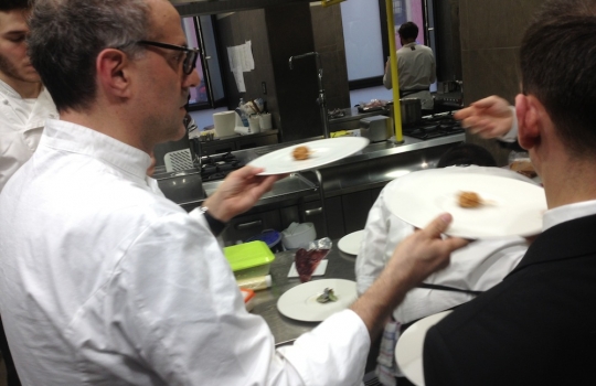 Photogallery






 
Modena’s colonnades, 186 thousand inhabitants and 3 restaurants with at least one Michelin star: Hostaria del Mare (1), Erba del Re (1) and Osteria Francescana (3 stars), our destination
 








Yellow and red tones prevail








The city still bears the signs of the May 2012 earthquake. On May 4th 2013, the day of our visit, a 3.8 magnitude earthquake was registered













By chance, Giuseppe Palmieri, maître and sommelier, appears from the grey door








Palmieri, 38, born in Matera. His first service in Francescana was on September 12th 2000








The old entrance to the restaurant, at number 24 in Via della Stella - as on the opening in 1995. It changed in September 2012: today you enter from number 22. Funnily enough, Google Maps is still set on the old entrance








The present entrance doors








Let’s start








After the latest renovations, the transit areas inside the Osteria appear as a contemporary art gallery








Mario Schifano’s world map








"Tourists", Maurizio Cattelan’s famous pigeons








Underneath the pigeons, Gavin Turk’s “Trashbag”








Three rooms, 12 tables, between 20 to 35 guests. 40% guests are Italian








Every table is illuminated by Davide Groppi’s Sampei lamp: if tables are moved, light follows








Francescana receives 150 reservations every day. But it also suffers from clients not showing up: on average, one table every week is booked but then guests don’t come








Right behind the kitchen, there’s the prêt-à-porter cellar








"In the central cellar, we only keep great vintages and larger bottles of what we consider to be great wines", Beppe Palmieri explains








1,600 wines are listed at Osteria Francescana, with a deep wine list which includes different vintages of the same wine








"A true celebration of wine "








The Ferrari coat, hanging in the cellar: Maranello is only 17 km away from Modena








Jean Todt, Michael Schumacher, Fernando Alonso: Ferrari’s “prancing horse” is at home in Via Stella








Gabrio Bini’s wines, from Pantelleria, a real fetish for Palmieri













Hanging from the ceiling, a nice selection of cured meats from Emilia








Bread made with mother yeast, the premise to a journey which will alternate great classics with very contemporary dishes








Massimo Bottura. Fifty years old last September, he is chef since 1986, the year of Trattoria del Campazzo in Nonantola. His first masters: Lidia Cristoni and Georges Cogny








He’s glowing: a few days ago his restaurant climbed, for the first time, onto the podium of the World's 50Best, a prize that is acquiring an increasing weight and authority. "The thing that makes me the happiest", he says, "is not so much the third place, but the fact that we’ve been in the highest positions for a few years now". True: 13th in 2009, 6th in 2010, 4th in 2011, 5th in 2012, 3rd in 2013








The now famous grey New Balance 993, a real emblem for the chef, friend of Jason Weis, president of the company in Massachusetts. The insole, however, is local: "In Emilia the sector is state-of-the-art", he says








"Are we ready?"








Almond granita with capers, bergamot and coffee cream 
Bottura and Palmieri’s journey across Italy starts from the bottom. And sails off from the Sicilian inland, with a classic granita which in Modena crumbles Adria-style, the wall that divides sweet from savoury, using the picklock of bitterness: Pantelleria capers, wild oregano but also bergamot, a coffee concentrate and vanilla scented salt. To pair with the first part of the meal, Sorriso di Cielo malvasia dei colli piacentini








Mediterranean Macaroon 
Next to the granita, two peculiar macaroons: the first is made with minced anchovies and sardines, the second with oysters and seaweeds. This is a classic scheme in Bottura’scuisine: his ironic turning the order of the dishes, from starter to dessert, upside down, and using popular raw materials instead of ingredients that are emblematic of élite cuisine. «While feet are sinking in the ground, the head is free to move everywhere», is one of his most famous quotes








Tempura of freshwater aulla with carpione ice-cream
Carpione ice-cream on a tempura of freshwater aulla – these fish are similar and slightly bigger than whitebait. The tempura is made by quickly placing the cold batter in boiling oil








Bread and croissants








Grissini








Baccalà Mare Nostrum 
We move up the Tyrrhenian sea to find this salted codfish cooked at low temperature and then seasoned with a touch of Naples and the Amalfi coast, that is to say with an emulsion made with hot oil with tomato vegetal liquid, olives, the zest of Sorrento’s super lemons and some anchovy colatura. These aromas crack with the scented bread on top








40 year old Denis Bretta explains the dishes as if from a book. Once at Restaurant Fini in Modena, for the past year and a half he’s been the manager responsible for the service in the restaurant. But don’t ask Palmieri to explain his role, as he’s abolished all hierarchies: "In our restaurant there are no commis or chef de rang. At a time when titles are so abused, I prefer for us to be all colleagues. All waiters."








How to burn sardines in three days 
Another journey, another horizon, the Adriatic Sea between Romagna and Ancona. A new camouflaged expression: these are not sardines (and they aren’t burnt either) but they are small sea-rock mullet, marinated for 3 days, then seared on one side on a grill, and filled like a sandwich with some (very sweet) scampi cream, and covered with vegetable ashes, aromatic herbs and lemon zest. “I wanted to make fun of the Marche-Romagna habit of grilling everything”, the chef says, “with lemon, garlic and parsley always added later to fix everything”









Rice, between fresh and sea water 
Recalling the Po estuary with freshwater and brackish sensations. The freshwater flavours cover the surface of the oyster which prevails on the river bed. And in the end, catfish, carp, vegetable chlorophyll and carpione win once again








 
A journey to Modena: Adriatic eel, polenta, Campanine apple jelly and saba
Another fluvial odyssey, presented for the first time at Identità Milano in 2011. The Adriatic eel travels across Veneto (with the polenta cream), Mantua (the Campanine apple jelly), the countryside of Modena (with the Saba lacquering, that is to say the mother of Aceto Balsamico) and stops in the centre of Modena (blackened powdered onion, a mimesis of the town’s canals)
 








Normandy
That is to say pre-salè lamb (hanging for 20 days) with an emulsion of oyster water, fresh seaweeds and caviar. On top, a green apple granita that recalls cider. “This is our tribute to Normandy”, Bretta says, “in Modena there are no enchanted beaches or breath-taking mountain tops. From Via Stella you can’t even see the Torre Ghirlandina. What guides us is the persistant strength of ideas, woven into the culture and into memories”








Giovanni Boroni’s Genziana from Trentino. A brilliant idea by Palmieri that acts as a bridge between the two dishes, Normandy (previous picture) and Think Green (next one). This distillate plays an immediate contrast with the sea-character of the first dish: "To me, harmony is what is left after a confrontation", B.P. says. And the confrontation is followed by the thought that spurs from the following match: water is added to the Genziana and the palate surprisingly longs to gulp it all. This is the perfect vehicle for the aromas of the genziana and "gives length" to the minerality of the wild herbs. "This serves to recall water, our true source of richness". Brilliant








Think Green
Vegetal chlorophyll, asparagus tops, pea cream, mushrooms, truffle, flowers, aromatic herbs and Parmigiano Reggiano curd. The idea of this dish came after observing the biological cycle of grazing cows, 4 seasons that sum up all of life. “This is what the cow eats, and what it returns to us, thanks to an extraordinary milk”, Bottura adds








Five ages of Parmigiano Reggiano 
A great classic from 1996, "when the textures in fact were 3", Palmieri points out. Today they are 5: 4 month ageing cream, 30 month demi-soufflè, 36 month mousse, 40 month crispy wafer, on top, “air” of 50 month Parmesan. (photo by Le Saucier)








A compression of pasta and beans 
Another great classic, this is a journey across Bottura’s experiences in the kitchen: Creme royal with pork rind, beans and foie gras (French tradition), rosemary air (the Spanish vanguard) and Parmesan crust (the Emilian essence) used instead of pasta. “This is a dish based on evolution, not revolution. I compressed my grandmother between Alain Ducasse and Ferran Adrià”








Snails under the grapevines 
Snails, aromatic chlorophyll on a bed of wild vegetables and herbs, with mushrooms, truffle and bulbs. After the cow’s life cycle, here comes that of the snail. "Once again, we’re chewing the territory: the best snails slither in the vineyards, among mineral, sapid and acid aromas"








A Frenchman’s dream of making pasta like an Italian 
Or, Ravioli with leeks, foie gras and truffle. We covered this in detail in Identità di Pasta issue number 27








Damijan Podversic’s Ribolla Gialla, a great wine by a wine producer from Gorizia inspired by Josko Gravner. It will support the following dish, without concealing it








A sharp knife is only served now. Another sign of the “allergy” to lengthy chewing that characterises most of contemporary high cuisine








Pigeon hunt 
And over to Bretta: "This is served in a balsamic sauce made with beetroots, which recalls blood. The salad is made with fake leaves, made by cutting out some tubers using some small stamps. These are then compressed in a vacuum with different types of vinegar. The horseradish is grated a few seconds before service, to give some velocity to the pigeon". Irony wins, since "pigeons are not hunted". The bird supplier is Franco Cazzamali from Cremona








Before the dessert, a trip to the restroom: vegetal notes prevail here too








A visit to the kitchen: capon stock





