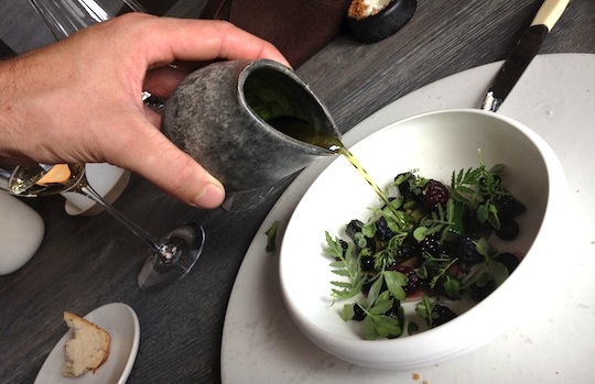 Galleria fotografica






In cammino verso il Noma. Il ristorante è al piano terra del palazzone più a sinistra. Per arrivarci dalla popolare insenatura di Nyhavn (il punto da cui è scattata la foto), occorre fare un bel giro. Ma si notano i lavori per la costruzione di un ponte. Che condurrà dritto all'insegna








Altra prospettiva sul Noma da Nyhavn. Il ristorante galleggia sulla Christianshavn, una delle tante isole artificiali che compongono Copenhagen








Di là del fiume, sulla lunga via che conduce allo spiazzo del Noma








Uno scenario molto tranquillo, di case pastello. Il silenzio è perché vanno tutti in bici













Al massimo si sente rombare qualche scafo








Il vascello davanti al Noma. Oltre a quella danese, sventolano le bandiere di Isole Far Oer e Groenlandia: le loro ambasciate sono nello stesso palazzo del ristorante. Coerenza nordica








Il retro del ristorante. L'80% delle 80 persone che lavorano al Noma viene a lavorare in bici, chef incluso








Dietro al ristorante, un'iscrizione ricorda i passeggeri scomparsi a bordo della danese Hans Hedtoft. Il transatlantico si scontrò il 30 gennaio 1959 contrò un iceberg in Groenlandia. Fu ritrovata solo una cintura di sicurezza
 








L'ingresso del ristorante, al civico 93 di Strandgade








La vista, ingresso alle spalle








Tra l'ingresso e la cucina a vista, spicca un corner di decoro simil-giapponese. A sinistra s'intravede Noma, time and place in Nordic Cuisine, edizioni Phaidon, un testo fondamentale per approfondire tutti i rivoli del Redzepi-mondo. La versione italiana si ordina qui








Una pianta di piccoli agrumi orla la cucina a vista








La porta d'ingresso vista dalla cucina








Le sedie, molto comode, sono anni Sessanta con schienali foderati di pelle di pecora, alcune più morbide di altre








I tavoli sono ampi e senza tovaglie. Attorno prevale il grigio e i colori rustici, sulle travi in legno del soffitto ma anche sulle divise dei ragazzi di sala








La finestra accanto al nostro tavolo








E' lo chef Rene Redzepi a introdurci al pasto: in un vaso di fiori danesi, l'unico pendaglio commestibile è una sorta di carta musica croccante (flatbread) di farina di malto all'aroma di ginepro. Nel piattino in basso, una deliziosa crème fraîche acida per intingerlo








Il flatbread è quello che svetta. "Ma se ci tenete, provate a mangiare anche i fiori", scherza Redzepi. Il cuoco scompare nelle segrete del Noma. Lo ritroveremo solo alla fine del pasto








Tutti i 14 appetizer si mangeranno con le mani. Unica posata, il coltello per tirar su e leccare la crème fraîche da sola (da fare quando tutti gli altri clienti son distratti, però)








Moss and Cep: Muschio di renna con polvere di funghi porcini. E' il corpo bianco, molto saporito ed evanescente, da intingere anch'esso nella crème fraîche
 








Crispy pork skin and black currant: Pelle di maiale croccante e ribes nero, lo strato più esterno. Aspro e croccante








Il ribes nero non ci lascerà prima di molto tempo








Blue mussels and celery: cozze e sedano. Solo due sono quelle buone








La parte inferiore del guscio è commestibile (ancora farina di malto)








Il quinto appetizer è nascosto in una deliziosa scatola di biscotti in latta della tradizione danese (chi non ricorda i Danish butter cookies?)








Cinque tondini, ma solo due "interessanti"








Si chiamano Cheese cookies, rocket and stems, letteralmente Biscotti al formaggio, ruchetta e gambi di erbe aromatiche, un felice snack potenzialmente riproducibile nei nord e nei sud del mondo








Appetizer #6: Potato and duck liver, Patate e fegato d'anatra: le patate croccanti sono in due strati e a mo' di sandwich racchiudono la mousse di fegato. La spolverata è di funghi trombette dei morti, disidratati e polverizzati, una tecnica che troveremo frequentemente








Dried carrot and sorrel, Carote grigliate a fuoco lento per 14 ore, disidratate e servite su polvere di fieno. Si intingono nell'emulsione di acetosella accanto. Un grande piatto perché di inattesa, energica acidità








Ottava entrée: Caramelized milk and cod liver, Biscotto di latte caramellato e fegato di merluzzo, quest'ultimo ghiacciato e pulito. Il secondo dona un aroma molto strong, che domina sul biscotto croccante. Per palati muscolari








Le uova dentro l'uovo








Pickled and smoked quails eggs, Uova di quaglia sbollentate, marinate e affumicate, un classico del Noma. Il tuorlo è completamente liquido








Col Veal fibres and söl, Filamenti di vitello e söl, decimo appetizer, entra in gioco per la prima volta un'alga di mare. E' il söl, appunto, dulse in inglese, Palmaria palmata nella tassonomia scientifica, un'alga rossa incastrata nei filamenti di vitello precedentemente tagliati sottili e poi fritti. Curioso l'impiatto a nido di ingredienti che alla fine incastrano terra e mare








Herb Toast and smoked cod roe, Toast alle erbe e uova di merluzzo affumicato, un'altra grandiosa tapa nordica da far su in due bocconi. Se non ricordiamo male, lo strato superiore è brodo di fegato d'anatra disidratato








Radish, soil and grass, Rapanello, "suolo" ed erba, un altro grande classico del Noma, un paesaggio commestibile di chiara genesi basca-adrianesca, molto replicato negli anni. Carote baby e rapanelli sono interrati in un "suolo" che è una crema di farina di malto con nocciole disidratate. Sotto ancora, uno yogurt di erbe. Finite le verdure, abbiamo chiesto dei cucchiaini per ripulire il suolo








Una foto (di spreadbutter) chiarisce meglio il contenuto del vasetto








Æbleskiver e muikku, penultimo appetizer, di concezione piuttosto recente. Un'antica tradizione dolce danese (Æbleskiver significa "piccoli pezzi di mela" ma la mela qui non c'è) è presentata in versione salata. Code e teste dei muikku, sorta di aringhe baby, sono infilzate in due bigné dall'impasto molto morbido con del ripieno di cetriolo marinato, ben riconoscibile al palato. L'aspetto dispone il cliente alla sfida ma la sua bizzarria visiva si scioglie presto in due bocconi morbidi, eleganti e deliziosi








Ultimo di 14 appetizer: Sorrel leaf and cricket paste, Foglia di acetosella (leggermente piccante) con pasta di grillo. Sì, proprio l'insetto dei prati, qui in consistenza di crema, inserita nel gambo dell'acetosella. Mettendo a fermentare grilli e orzo fermentato, Redzepi ha ottenuto una sorta di garum molto interessante, simile alla soia. Completa il piatto in foto, una granita di nasturzio ghiacciato








E il vino? Non producendo la Danimarca nettari di rilievo, è forse il capitolo meno allettante del Noma. La carta è un trionfo di vini ottenuti in climi freddi: francesi, tedeschi o austriaci soprattutto. Vini di acidità spinta che si combinano bene con le prevalenti acidità dei piatti. Le persone inquadrate nella foto hanno optato per il pairing coi succhi di frutta, quelli sì interessanti e autoctoni: il percorso prevede 7-8 succhi tra cui carote e ginepro, sedano e sedanorapa, cetriolo, eccetera. E i vini italiani? Pochi e tutti rossi, soprattutto di produttori di nebbiolo del Piemonte. "Ma li chiedono solo i norvegesi", ci raccontano








Terminati appetizer e main courses, sbirciamo i lavori in cucina. In primo piano, Samuel Nutter, sous chef inglese








Al centro, riconosciamo Matthew Orlando di San Diego, 35 anni e da 4 e mezzo head chef del Noma. Più tardi ci rivelerà che entro un paio d'anni aprirà il suo ristorante a Copenhagen. "E Renè che ne pensa?", chiediamo. "E' proprio lui a incoraggiarci a metterci in proprio", risponde Orlando. Vero, chiedere anche a Christian Puglisi








Ancora Orlando ci spiegherà che, tra sala, cucina, preparazioni e laboratorio, il Noma arriva a impiegare dall'alba a mezzanotte fino a 80 persone








La cucina prevede 7 comparti: il caldo, il freddo, la pasticceria, gli snack, produzione e mise-en-place, le preparazioni della squadra del mattino e la ricerca (su quest'ultima torneremo più avanti). Gli stagisti scelgono di lavorarci, sapendo di non essere pagati. Redzepi riceve un centinaio di curricula a settimana








Torniamo a tavola e troviamo nuove posate: rami appuntiti di sambuco








Servono a infilzare il primo delle portate "serie", Potato and snails, patate e lumache, servito in due piatti. Il primo è una terrina (rovente) di piccole deliziose patate affumicate e semiaffogate in una salsa al burro dolce e al tavolo spolverate con sale proprio di sambuco. Accanto, piccoli ceppi d'albero affumicati








Accanto, l'altra metà del piatto da infilzare coi bastoncini di sambuco: lumache glassate nel loro succo con burro dolce, olio al prezzemolo ed emulsione di piselli fermentati








Dopo 15 portate arrivano le posate. "Si torna alla civiltà", scherza il ragazzo di sala








...e arriva pure il pane, nascosto in una stoffa soffice con accanto due ciotoline che contengono burro da latte di capra e burro di grasso e crumble di maiale. Colesterolemici, vade retro








Solleviamo la stoffa: il pane è una pagnotta di lievito naturale di grano locale. La crosta è super-fragrante e il cuore molto sofficie e poroso








Cooked fava beans and beach herbs, Fave stufate gentilmente ed "erbe di spiaggia" (che poi sono diversi tipi di alghe di mare). Le fave sono fantastiche nella loro compattezza inaspettatamente dolce








Con la terza portata del ciclo "serio" veniamo ai ragazzi di sala: sono tutti molto professionali ma anche rilassati. Tra i 30 e i 40 anni, molti tatuati, ruotano di continuo al nostro tavolo: una trentina dei piatti sono stati serviti e illustrati da 10 camerieri diversi, molti dei quali cuochi dei livelli più alti della gerarchia. Il ragazzo in foto che ci serve Berries and cucumber, Bacche e cetrioli, si chiama Beau Clugston, è australiano e da poche ore è un nuovo sous-chef del Noma





