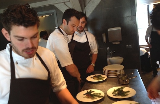 Galleria fotografica






In cammino verso il Noma. Il ristorante è al piano terra del palazzone più a sinistra. Per arrivarci dalla popolare insenatura di Nyhavn (il punto da cui è scattata la foto), occorre fare un bel giro. Ma si notano i lavori per la costruzione di un ponte. Che condurrà dritto all'insegna








Altra prospettiva sul Noma da Nyhavn. Il ristorante galleggia sulla Christianshavn, una delle tante isole artificiali che compongono Copenhagen








Di là del fiume, sulla lunga via che conduce allo spiazzo del Noma








Uno scenario molto tranquillo, di case pastello. Il silenzio è perché vanno tutti in bici













Al massimo si sente rombare qualche scafo








Il vascello davanti al Noma. Oltre a quella danese, sventolano le bandiere di Isole Far Oer e Groenlandia: le loro ambasciate sono nello stesso palazzo del ristorante. Coerenza nordica








Il retro del ristorante. L'80% delle 80 persone che lavorano al Noma viene a lavorare in bici, chef incluso








Dietro al ristorante, un'iscrizione ricorda i passeggeri scomparsi a bordo della danese Hans Hedtoft. Il transatlantico si scontrò il 30 gennaio 1959 contrò un iceberg in Groenlandia. Fu ritrovata solo una cintura di sicurezza
 








L'ingresso del ristorante, al civico 93 di Strandgade








La vista, ingresso alle spalle








Tra l'ingresso e la cucina a vista, spicca un corner di decoro simil-giapponese. A sinistra s'intravede Noma, time and place in Nordic Cuisine, edizioni Phaidon, un testo fondamentale per approfondire tutti i rivoli del Redzepi-mondo. La versione italiana si ordina qui








Una pianta di piccoli agrumi orla la cucina a vista








La porta d'ingresso vista dalla cucina








Le sedie, molto comode, sono anni Sessanta con schienali foderati di pelle di pecora, alcune più morbide di altre








I tavoli sono ampi e senza tovaglie. Attorno prevale il grigio e i colori rustici, sulle travi in legno del soffitto ma anche sulle divise dei ragazzi di sala








La finestra accanto al nostro tavolo








E' lo chef Rene Redzepi a introdurci al pasto: in un vaso di fiori danesi, l'unico pendaglio commestibile è una sorta di carta musica croccante (flatbread) di farina di malto all'aroma di ginepro. Nel piattino in basso, una deliziosa crème fraîche acida per intingerlo








Il flatbread è quello che svetta. "Ma se ci tenete, provate a mangiare anche i fiori", scherza Redzepi. Il cuoco scompare nelle segrete del Noma. Lo ritroveremo solo alla fine del pasto








Tutti i 14 appetizer si mangeranno con le mani. Unica posata, il coltello per tirar su e leccare la crème fraîche da sola (da fare quando tutti gli altri clienti son distratti, però)








Moss and Cep: Muschio di renna con polvere di funghi porcini. E' il corpo bianco, molto saporito ed evanescente, da intingere anch'esso nella crème fraîche
 








Crispy pork skin and black currant: Pelle di maiale croccante e ribes nero, lo strato più esterno. Aspro e croccante








Il ribes nero non ci lascerà prima di molto tempo








Blue mussels and celery: cozze e sedano. Solo due sono quelle buone








La parte inferiore del guscio è commestibile (ancora farina di malto)








Il quinto appetizer è nascosto in una deliziosa scatola di biscotti in latta della tradizione danese (chi non ricorda i Danish butter cookies?)








Cinque tondini, ma solo due "interessanti"








Si chiamano Cheese cookies, rocket and stems, letteralmente Biscotti al formaggio, ruchetta e gambi di erbe aromatiche, un felice snack potenzialmente riproducibile nei nord e nei sud del mondo








Appetizer #6: Potato and duck liver, Patate e fegato d'anatra: le patate croccanti sono in due strati e a mo' di sandwich racchiudono la mousse di fegato. La spolverata è di funghi trombette dei morti, disidratati e polverizzati, una tecnica che troveremo frequentemente








Dried carrot and sorrel, Carote grigliate a fuoco lento per 14 ore, disidratate e servite su polvere di fieno. Si intingono nell'emulsione di acetosella accanto. Un grande piatto perché di inattesa, energica acidità








Ottava entrée: Caramelized milk and cod liver, Biscotto di latte caramellato e fegato di merluzzo, quest'ultimo ghiacciato e pulito. Il secondo dona un aroma molto strong, che domina sul biscotto croccante. Per palati muscolari








Le uova dentro l'uovo








Pickled and smoked quails eggs, Uova di quaglia sbollentate, marinate e affumicate, un classico del Noma. Il tuorlo è completamente liquido








Col Veal fibres and söl, Filamenti di vitello e söl, decimo appetizer, entra in gioco per la prima volta un'alga di mare. E' il söl, appunto, dulse in inglese, Palmaria palmata nella tassonomia scientifica, un'alga rossa incastrata nei filamenti di vitello precedentemente tagliati sottili e poi fritti. Curioso l'impiatto a nido di ingredienti che alla fine incastrano terra e mare








Herb Toast and smoked cod roe, Toast alle erbe e uova di merluzzo affumicato, un'altra grandiosa tapa nordica da far su in due bocconi. Se non ricordiamo male, lo strato superiore è brodo di fegato d'anatra disidratato








Radish, soil and grass, Rapanello, "suolo" ed erba, un altro grande classico del Noma, un paesaggio commestibile di chiara genesi basca-adrianesca, molto replicato negli anni. Carote baby e rapanelli sono interrati in un "suolo" che è una crema di farina di malto con nocciole disidratate. Sotto ancora, uno yogurt di erbe. Finite le verdure, abbiamo chiesto dei cucchiaini per ripulire il suolo








Una foto (di spreadbutter) chiarisce meglio il contenuto del vasetto








Æbleskiver e muikku, penultimo appetizer, di concezione piuttosto recente. Un'antica tradizione dolce danese (Æbleskiver significa "piccoli pezzi di mela" ma la mela qui non c'è) è presentata in versione salata. Code e teste dei muikku, sorta di aringhe baby, sono infilzate in due bigné dall'impasto molto morbido con del ripieno di cetriolo marinato, ben riconoscibile al palato. L'aspetto dispone il cliente alla sfida ma la sua bizzarria visiva si scioglie presto in due bocconi morbidi, eleganti e deliziosi








Ultimo di 14 appetizer: Sorrel leaf and cricket paste, Foglia di acetosella (leggermente piccante) con pasta di grillo. Sì, proprio l'insetto dei prati, qui in consistenza di crema, inserita nel gambo dell'acetosella. Mettendo a fermentare grilli e orzo fermentato, Redzepi ha ottenuto una sorta di garum molto interessante, simile alla soia. Completa il piatto in foto, una granita di nasturzio ghiacciato








E il vino? Non producendo la Danimarca nettari di rilievo, è forse il capitolo meno allettante del Noma. La carta è un trionfo di vini ottenuti in climi freddi: francesi, tedeschi o austriaci soprattutto. Vini di acidità spinta che si combinano bene con le prevalenti acidità dei piatti. Le persone inquadrate nella foto hanno optato per il pairing coi succhi di frutta, quelli sì interessanti e autoctoni: il percorso prevede 7-8 succhi tra cui carote e ginepro, sedano e sedanorapa, cetriolo, eccetera. E i vini italiani? Pochi e tutti rossi, soprattutto di produttori di nebbiolo del Piemonte. "Ma li chiedono solo i norvegesi", ci raccontano








Terminati appetizer e main courses, sbirciamo i lavori in cucina. In primo piano, Samuel Nutter, sous chef inglese





