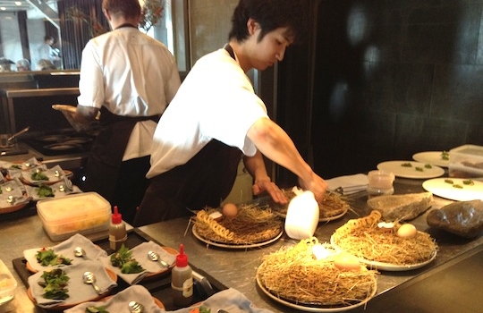 Galleria fotografica






In cammino verso il Noma. Il ristorante è al piano terra del palazzone più a sinistra. Per arrivarci dalla popolare insenatura di Nyhavn (il punto da cui è scattata la foto), occorre fare un bel giro. Ma si notano i lavori per la costruzione di un ponte. Che condurrà dritto all'insegna








Altra prospettiva sul Noma da Nyhavn. Il ristorante galleggia sulla Christianshavn, una delle tante isole artificiali che compongono Copenhagen








Di là del fiume, sulla lunga via che conduce allo spiazzo del Noma








Uno scenario molto tranquillo, di case pastello. Il silenzio è perché vanno tutti in bici













Al massimo si sente rombare qualche scafo








Il vascello davanti al Noma. Oltre a quella danese, sventolano le bandiere di Isole Far Oer e Groenlandia: le loro ambasciate sono nello stesso palazzo del ristorante. Coerenza nordica








Il retro del ristorante. L'80% delle 80 persone che lavorano al Noma viene a lavorare in bici, chef incluso








Dietro al ristorante, un'iscrizione ricorda i passeggeri scomparsi a bordo della danese Hans Hedtoft. Il transatlantico si scontrò il 30 gennaio 1959 contrò un iceberg in Groenlandia. Fu ritrovata solo una cintura di sicurezza
 








L'ingresso del ristorante, al civico 93 di Strandgade








La vista, ingresso alle spalle








Tra l'ingresso e la cucina a vista, spicca un corner di decoro simil-giapponese. A sinistra s'intravede Noma, time and place in Nordic Cuisine, edizioni Phaidon, un testo fondamentale per approfondire tutti i rivoli del Redzepi-mondo. La versione italiana si ordina qui








Una pianta di piccoli agrumi orla la cucina a vista








La porta d'ingresso vista dalla cucina








Le sedie, molto comode, sono anni Sessanta con schienali foderati di pelle di pecora, alcune più morbide di altre








I tavoli sono ampi e senza tovaglie. Attorno prevale il grigio e i colori rustici, sulle travi in legno del soffitto ma anche sulle divise dei ragazzi di sala








La finestra accanto al nostro tavolo








E' lo chef Rene Redzepi a introdurci al pasto: in un vaso di fiori danesi, l'unico pendaglio commestibile è una sorta di carta musica croccante (flatbread) di farina di malto all'aroma di ginepro. Nel piattino in basso, una deliziosa crème fraîche acida per intingerlo








Il flatbread è quello che svetta. "Ma se ci tenete, provate a mangiare anche i fiori", scherza Redzepi. Il cuoco scompare nelle segrete del Noma. Lo ritroveremo solo alla fine del pasto








Tutti i 14 appetizer si mangeranno con le mani. Unica posata, il coltello per tirar su e leccare la crème fraîche da sola (da fare quando tutti gli altri clienti son distratti, però)








Moss and Cep: Muschio di renna con polvere di funghi porcini. E' il corpo bianco, molto saporito ed evanescente, da intingere anch'esso nella crème fraîche
 








Crispy pork skin and black currant: Pelle di maiale croccante e ribes nero, lo strato più esterno. Aspro e croccante








Il ribes nero non ci lascerà prima di molto tempo








Blue mussels and celery: cozze e sedano. Solo due sono quelle buone








La parte inferiore del guscio è commestibile (ancora farina di malto)








Il quinto appetizer è nascosto in una deliziosa scatola di biscotti in latta della tradizione danese (chi non ricorda i Danish butter cookies?)








Cinque tondini, ma solo due "interessanti"








Si chiamano Cheese cookies, rocket and stems, letteralmente Biscotti al formaggio, ruchetta e gambi di erbe aromatiche, un felice snack potenzialmente riproducibile nei nord e nei sud del mondo








Appetizer #6: Potato and duck liver, Patate e fegato d'anatra: le patate croccanti sono in due strati e a mo' di sandwich racchiudono la mousse di fegato. La spolverata è di funghi trombette dei morti, disidratati e polverizzati, una tecnica che troveremo frequentemente








Dried carrot and sorrel, Carote grigliate a fuoco lento per 14 ore, disidratate e servite su polvere di fieno. Si intingono nell'emulsione di acetosella accanto. Un grande piatto perché di inattesa, energica acidità








Ottava entrée: Caramelized milk and cod liver, Biscotto di latte caramellato e fegato di merluzzo, quest'ultimo ghiacciato e pulito. Il secondo dona un aroma molto strong, che domina sul biscotto croccante. Per palati muscolari








Le uova dentro l'uovo








Pickled and smoked quails eggs, Uova di quaglia sbollentate, marinate e affumicate, un classico del Noma. Il tuorlo è completamente liquido








Col Veal fibres and söl, Filamenti di vitello e söl, decimo appetizer, entra in gioco per la prima volta un'alga di mare. E' il söl, appunto, dulse in inglese, Palmaria palmata nella tassonomia scientifica, un'alga rossa incastrata nei filamenti di vitello precedentemente tagliati sottili e poi fritti. Curioso l'impiatto a nido di ingredienti che alla fine incastrano terra e mare








Herb Toast and smoked cod roe, Toast alle erbe e uova di merluzzo affumicato, un'altra grandiosa tapa nordica da far su in due bocconi. Se non ricordiamo male, lo strato superiore è brodo di fegato d'anatra disidratato








Radish, soil and grass, Rapanello, "suolo" ed erba, un altro grande classico del Noma, un paesaggio commestibile di chiara genesi basca-adrianesca, molto replicato negli anni. Carote baby e rapanelli sono interrati in un "suolo" che è una crema di farina di malto con nocciole disidratate. Sotto ancora, uno yogurt di erbe. Finite le verdure, abbiamo chiesto dei cucchiaini per ripulire il suolo








Una foto (di spreadbutter) chiarisce meglio il contenuto del vasetto








Æbleskiver e muikku, penultimo appetizer, di concezione piuttosto recente. Un'antica tradizione dolce danese (Æbleskiver significa "piccoli pezzi di mela" ma la mela qui non c'è) è presentata in versione salata. Code e teste dei muikku, sorta di aringhe baby, sono infilzate in due bigné dall'impasto molto morbido con del ripieno di cetriolo marinato, ben riconoscibile al palato. L'aspetto dispone il cliente alla sfida ma la sua bizzarria visiva si scioglie presto in due bocconi morbidi, eleganti e deliziosi








Ultimo di 14 appetizer: Sorrel leaf and cricket paste, Foglia di acetosella (leggermente piccante) con pasta di grillo. Sì, proprio l'insetto dei prati, qui in consistenza di crema, inserita nel gambo dell'acetosella. Mettendo a fermentare grilli e orzo fermentato, Redzepi ha ottenuto una sorta di garum molto interessante, simile alla soia. Completa il piatto in foto, una granita di nasturzio ghiacciato








E il vino? Non producendo la Danimarca nettari di rilievo, è forse il capitolo meno allettante del Noma. La carta è un trionfo di vini ottenuti in climi freddi: francesi, tedeschi o austriaci soprattutto. Vini di acidità spinta che si combinano bene con le prevalenti acidità dei piatti. Le persone inquadrate nella foto hanno optato per il pairing coi succhi di frutta, quelli sì interessanti e autoctoni: il percorso prevede 7-8 succhi tra cui carote e ginepro, sedano e sedanorapa, cetriolo, eccetera. E i vini italiani? Pochi e tutti rossi, soprattutto di produttori di nebbiolo del Piemonte. "Ma li chiedono solo i norvegesi", ci raccontano








Terminati appetizer e main courses, sbirciamo i lavori in cucina. In primo piano, Samuel Nutter, sous chef inglese








Al centro, riconosciamo Matthew Orlando di San Diego, 35 anni e da 4 e mezzo head chef del Noma. Più tardi ci rivelerà che entro un paio d'anni aprirà il suo ristorante a Copenhagen. "E Renè che ne pensa?", chiediamo. "E' proprio lui a incoraggiarci a metterci in proprio", risponde Orlando. Vero, chiedere anche a Christian Puglisi








Ancora Orlando ci spiegherà che, tra sala, cucina, preparazioni e laboratorio, il Noma arriva a impiegare dall'alba a mezzanotte fino a 80 persone





