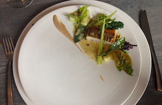 Galleria fotografica






In cammino verso il Noma. Il ristorante è al piano terra del palazzone più a sinistra. Per arrivarci dalla popolare insenatura di Nyhavn (il punto da cui è scattata la foto), occorre fare un bel giro. Ma si notano i lavori per la costruzione di un ponte. Che condurrà dritto all'insegna








Altra prospettiva sul Noma da Nyhavn. Il ristorante galleggia sulla Christianshavn, una delle tante isole artificiali che compongono Copenhagen








Di là del fiume, sulla lunga via che conduce allo spiazzo del Noma








Uno scenario molto tranquillo, di case pastello. Il silenzio è perché vanno tutti in bici













Al massimo si sente rombare qualche scafo








Il vascello davanti al Noma. Oltre a quella danese, sventolano le bandiere di Isole Far Oer e Groenlandia: le loro ambasciate sono nello stesso palazzo del ristorante. Coerenza nordica








Il retro del ristorante. L'80% delle 80 persone che lavorano al Noma viene a lavorare in bici, chef incluso








Dietro al ristorante, un'iscrizione ricorda i passeggeri scomparsi a bordo della danese Hans Hedtoft. Il transatlantico si scontrò il 30 gennaio 1959 contrò un iceberg in Groenlandia. Fu ritrovata solo una cintura di sicurezza
 








L'ingresso del ristorante, al civico 93 di Strandgade








La vista, ingresso alle spalle








Tra l'ingresso e la cucina a vista, spicca un corner di decoro simil-giapponese. A sinistra s'intravede Noma, time and place in Nordic Cuisine, edizioni Phaidon, un testo fondamentale per approfondire tutti i rivoli del Redzepi-mondo. La versione italiana si ordina qui








Una pianta di piccoli agrumi orla la cucina a vista








La porta d'ingresso vista dalla cucina








Le sedie, molto comode, sono anni Sessanta con schienali foderati di pelle di pecora, alcune più morbide di altre








I tavoli sono ampi e senza tovaglie. Attorno prevale il grigio e i colori rustici, sulle travi in legno del soffitto ma anche sulle divise dei ragazzi di sala








La finestra accanto al nostro tavolo








E' lo chef Rene Redzepi a introdurci al pasto: in un vaso di fiori danesi, l'unico pendaglio commestibile è una sorta di carta musica croccante (flatbread) di farina di malto all'aroma di ginepro. Nel piattino in basso, una deliziosa crème fraîche acida per intingerlo








Il flatbread è quello che svetta. "Ma se ci tenete, provate a mangiare anche i fiori", scherza Redzepi. Il cuoco scompare nelle segrete del Noma. Lo ritroveremo solo alla fine del pasto








Tutti i 14 appetizer si mangeranno con le mani. Unica posata, il coltello per tirar su e leccare la crème fraîche da sola (da fare quando tutti gli altri clienti son distratti, però)








Moss and Cep: Muschio di renna con polvere di funghi porcini. E' il corpo bianco, molto saporito ed evanescente, da intingere anch'esso nella crème fraîche
 








Crispy pork skin and black currant: Pelle di maiale croccante e ribes nero, lo strato più esterno. Aspro e croccante








Il ribes nero non ci lascerà prima di molto tempo








Blue mussels and celery: cozze e sedano. Solo due sono quelle buone








La parte inferiore del guscio è commestibile (ancora farina di malto)








Il quinto appetizer è nascosto in una deliziosa scatola di biscotti in latta della tradizione danese (chi non ricorda i Danish butter cookies?)








Cinque tondini, ma solo due "interessanti"








Si chiamano Cheese cookies, rocket and stems, letteralmente Biscotti al formaggio, ruchetta e gambi di erbe aromatiche, un felice snack potenzialmente riproducibile nei nord e nei sud del mondo








Appetizer #6: Potato and duck liver, Patate e fegato d'anatra: le patate croccanti sono in due strati e a mo' di sandwich racchiudono la mousse di fegato. La spolverata è di funghi trombette dei morti, disidratati e polverizzati, una tecnica che troveremo frequentemente








Dried carrot and sorrel, Carote grigliate a fuoco lento per 14 ore, disidratate e servite su polvere di fieno. Si intingono nell'emulsione di acetosella accanto. Un grande piatto perché di inattesa, energica acidità








Ottava entrée: Caramelized milk and cod liver, Biscotto di latte caramellato e fegato di merluzzo, quest'ultimo ghiacciato e pulito. Il secondo dona un aroma molto strong, che domina sul biscotto croccante. Per palati muscolari








Le uova dentro l'uovo








Pickled and smoked quails eggs, Uova di quaglia sbollentate, marinate e affumicate, un classico del Noma. Il tuorlo è completamente liquido








Col Veal fibres and söl, Filamenti di vitello e söl, decimo appetizer, entra in gioco per la prima volta un'alga di mare. E' il söl, appunto, dulse in inglese, Palmaria palmata nella tassonomia scientifica, un'alga rossa incastrata nei filamenti di vitello precedentemente tagliati sottili e poi fritti. Curioso l'impiatto a nido di ingredienti che alla fine incastrano terra e mare








Herb Toast and smoked cod roe, Toast alle erbe e uova di merluzzo affumicato, un'altra grandiosa tapa nordica da far su in due bocconi. Se non ricordiamo male, lo strato superiore è brodo di fegato d'anatra disidratato








Radish, soil and grass, Rapanello, "suolo" ed erba, un altro grande classico del Noma, un paesaggio commestibile di chiara genesi basca-adrianesca, molto replicato negli anni. Carote baby e rapanelli sono interrati in un "suolo" che è una crema di farina di malto con nocciole disidratate. Sotto ancora, uno yogurt di erbe. Finite le verdure, abbiamo chiesto dei cucchiaini per ripulire il suolo








Una foto (di spreadbutter) chiarisce meglio il contenuto del vasetto








Æbleskiver e muikku, penultimo appetizer, di concezione piuttosto recente. Un'antica tradizione dolce danese (Æbleskiver significa "piccoli pezzi di mela" ma la mela qui non c'è) è presentata in versione salata. Code e teste dei muikku, sorta di aringhe baby, sono infilzate in due bigné dall'impasto molto morbido con del ripieno di cetriolo marinato, ben riconoscibile al palato. L'aspetto dispone il cliente alla sfida ma la sua bizzarria visiva si scioglie presto in due bocconi morbidi, eleganti e deliziosi








Ultimo di 14 appetizer: Sorrel leaf and cricket paste, Foglia di acetosella (leggermente piccante) con pasta di grillo. Sì, proprio l'insetto dei prati, qui in consistenza di crema, inserita nel gambo dell'acetosella. Mettendo a fermentare grilli e orzo fermentato, Redzepi ha ottenuto una sorta di garum molto interessante, simile alla soia. Completa il piatto in foto, una granita di nasturzio ghiacciato








E il vino? Non producendo la Danimarca nettari di rilievo, è forse il capitolo meno allettante del Noma. La carta è un trionfo di vini ottenuti in climi freddi: francesi, tedeschi o austriaci soprattutto. Vini di acidità spinta che si combinano bene con le prevalenti acidità dei piatti. Le persone inquadrate nella foto hanno optato per il pairing coi succhi di frutta, quelli sì interessanti e autoctoni: il percorso prevede 7-8 succhi tra cui carote e ginepro, sedano e sedanorapa, cetriolo, eccetera. E i vini italiani? Pochi e tutti rossi, soprattutto di produttori di nebbiolo del Piemonte. "Ma li chiedono solo i norvegesi", ci raccontano








Terminati appetizer e main courses, sbirciamo i lavori in cucina. In primo piano, Samuel Nutter, sous chef inglese








Al centro, riconosciamo Matthew Orlando di San Diego, 35 anni e da 4 e mezzo head chef del Noma. Più tardi ci rivelerà che entro un paio d'anni aprirà il suo ristorante a Copenhagen. "E Renè che ne pensa?", chiediamo. "E' proprio lui a incoraggiarci a metterci in proprio", risponde Orlando. Vero, chiedere anche a Christian Puglisi








Ancora Orlando ci spiegherà che, tra sala, cucina, preparazioni e laboratorio, il Noma arriva a impiegare dall'alba a mezzanotte fino a 80 persone








La cucina prevede 7 comparti: il caldo, il freddo, la pasticceria, gli snack, produzione e mise-en-place, le preparazioni della squadra del mattino e la ricerca (su quest'ultima torneremo più avanti). Gli stagisti scelgono di lavorarci, sapendo di non essere pagati. Redzepi riceve un centinaio di curricula a settimana








Torniamo a tavola e troviamo nuove posate: rami appuntiti di sambuco








Servono a infilzare il primo delle portate "serie", Potato and snails, patate e lumache, servito in due piatti. Il primo è una terrina (rovente) di piccole deliziose patate affumicate e semiaffogate in una salsa al burro dolce e al tavolo spolverate con sale proprio di sambuco. Accanto, piccoli ceppi d'albero affumicati








Accanto, l'altra metà del piatto da infilzare coi bastoncini di sambuco: lumache glassate nel loro succo con burro dolce, olio al prezzemolo ed emulsione di piselli fermentati








Dopo 15 portate arrivano le posate. "Si torna alla civiltà", scherza il ragazzo di sala








...e arriva pure il pane, nascosto in una stoffa soffice con accanto due ciotoline che contengono burro da latte di capra e burro di grasso e crumble di maiale. Colesterolemici, vade retro








Solleviamo la stoffa: il pane è una pagnotta di lievito naturale di grano locale. La crosta è super-fragrante e il cuore molto sofficie e poroso








Cooked fava beans and beach herbs, Fave stufate gentilmente ed "erbe di spiaggia" (che poi sono diversi tipi di alghe di mare). Le fave sono fantastiche nella loro compattezza inaspettatamente dolce








Con la terza portata del ciclo "serio" veniamo ai ragazzi di sala: sono tutti molto professionali ma anche rilassati. Tra i 30 e i 40 anni, molti tatuati, ruotano di continuo al nostro tavolo: una trentina dei piatti sono stati serviti e illustrati da 10 camerieri diversi, molti dei quali cuochi dei livelli più alti della gerarchia. Il ragazzo in foto che ci serve Berries and cucumber, Bacche e cetrioli, si chiama Beau Clugston, è australiano e da poche ore è un nuovo sous-chef del Noma








Ai frutti di bosco e insalata di cetrioli si unisce del succo di camomilla...








...et voilà








Insalata di brown crab (granchi atlantici), tuorlo d'uovo, erbe di campo e il rosso sono le uova del granchio. I ragazzi si raccomandano di fare attenzione perchè potrebbe esserci del carapace o delle chele: la carne del granchio è stata rimossa tutta a mano. Noi ci scontriamo solo con un fresco schiaffo iodato








Accanto alle langoustine, scampi norvegesi, torna l'alga söl, questa volta in forma di emulsione con acqua di ostriche. I puntini rossi sono segale disidratata








Cavolfiore e pino, crema e rafano. Pensi a una capasanta e invece è un trancio di cavolfiore quello che spunta da sotto gli aghi di pino. E' ricavato dalla parte alta dell'ortaggio, arrostito a arricchito con gli aromi di pino, abete, ginepro e rafano. L'orto e il silvestre





