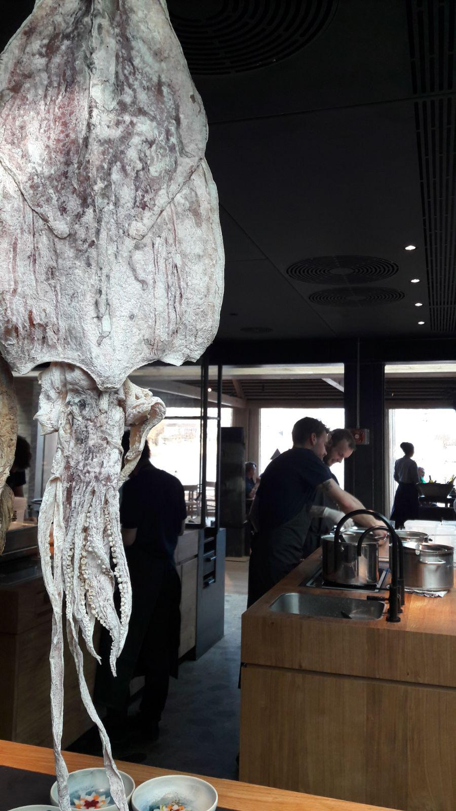 Photogallery






Noma 2.0 is in Christianshavn, the same neighbourhood as the first Noma. They’re 1.5 km apart, a 15 minutes’ walk. This picture shows the distance: to the right, there’s the warehouse of the old location (in Strandgade 93), to the left the smokestacks of Amager Bakke, the futuristic incinerator below which stands the new Noma (in Refshalevej 96)









Weather permitting, you can have a peaceful walk between the previous Noma to today’s Noma 









The new Noma is on an isthmus surrounded by canals. In the future they also want to reclaim some small parts for hydroponic farming









Bucolic scene with incinerator









Bikes left outside Noma. It’s the favourite means of transport among employees and interns









The long path taking you to the restaurant. The fence on the left shows how works are still in progress









On the two sides of the path there are the two new sections of the "Noma village", each with its specialty: grill, hot dishes, snacks, fermentations... In one month’s time, behind the fence we’ll have greenhouses, the test kitchen and the bread making area









To the left, before arriving at the restaurant, the future test kitchen. This will be run by Danish Mette Søberg with Riccardo Canella. "My first challenge?", reveals the latter, for a long time sous chef here, "is to work on the extraction of essential oils" 









The future Test Kitchen









The temporary gangway to the restaurant









Looking from the door to the restaurant, there’s a lake and the smokestacks puffing vapour from the Amager Bakke incinerator. It’s a futuristic project, both in terms of sustainability and architecture. It’s also known as Amager Slope or Copenhill, and its author is starchitect Bjarke Ingels, the same who designed the new Noma. Gradually opened in 2017, it transforms waste into electricity. The goal is to donate electricity to 62500 houses and hot water to 160000. It’s part of an ambitious project to transform Copenhagen into the first city in the world in terms of zero carbon dioxide emissions by 2025. By autumn this year, Amager Slope should open its ski slope, a climbing wall and a hiking track. You’ll be able to slalom on top of the incinerator









The windows from the dining room









Work is still in progress (photo taken on Thursday 22nd February 2018)









Traces of the old building, with barbwire. During WWII, they built bombs here









A view of the dining room at night (photo from Instagram/James Spreadbury)









The entrance to the restaurant









The usual ritual: a welcome from the entire staff, led by Rene Redzepi 









Behind the entrance, there are formaldehyde tanks with creatures from the abyss, shaped as in Damien Hirst’s works. The first image once you’re inside is to reproduce a Scandinavian village









The service kitchen is larger, more spacious and a completely open view from the dining room: "It’s the heart of our Scandinavian village", says Canella. There are 30 cooks working here now. 10 more, compared to the previous Noma









Large skylights above the cooks









There are currently more than 100 people working at Noma, of whom 63 are cooks - 26 employed, and 37 as interns









There’s fire in the kitchen, for the first time









On average, the dining room can host 40 people. "However", complains Redzepi, "there’s always someone who turns up with more people than the ones booked"









While the dining room is set, the outside space still need to be defined









The staff made the dining room decorations. There are no overly expensive designer objects









Dried fish









Seaweeds hanging from the ceiling









Dried octopus heads preserved in salt (with a balloon inside)






