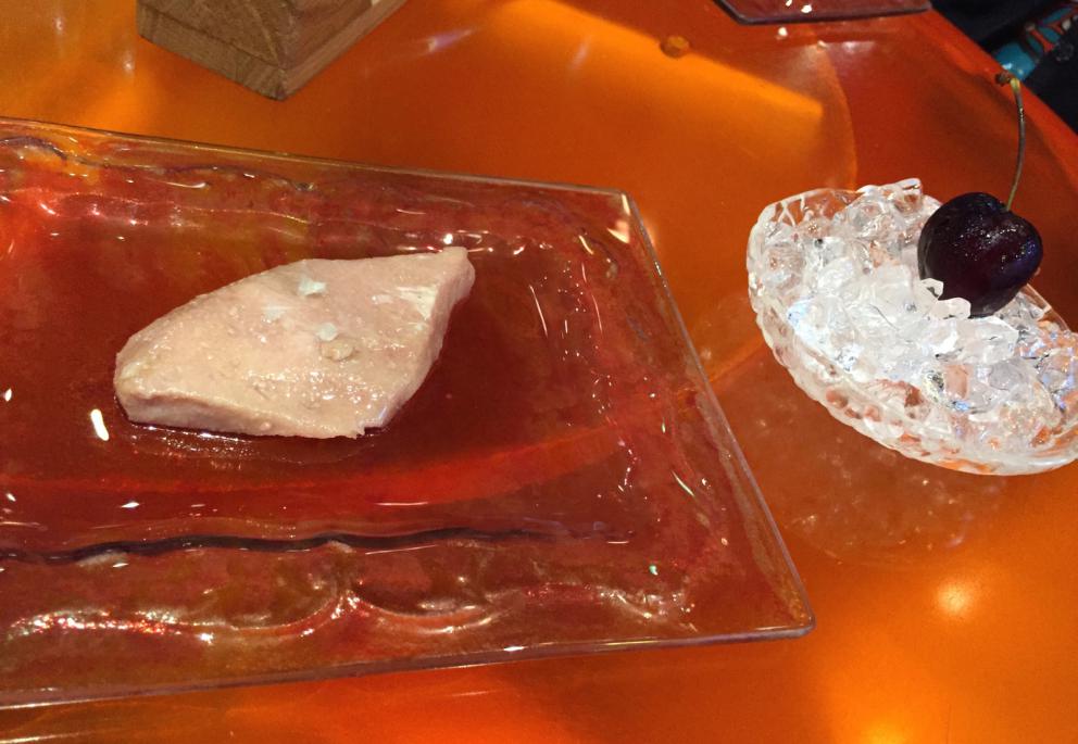 Galleria fotografica






Consommè de garbanzos. Prima che cominci il menu degustazione, viene portata al tavolo una bottiglia di vetro contenente del brodo freddo di ceci (in alto a destra). Ventitrè piatti dopo, alla fine del percorso "salato", verrà versato, in un bicchierino da grappa, del brodo caldo di jamon iberico da una teiera. Sopra ancora, la schiuma del brodo di ceci. Un caldo-freddo speciale (foto @ticketsbar instagram)









Tosta de pollo y anchoa. Primo piatto: toast di pelle di pollo con lisca di acciuga. A lato, una crema di acciughe composta da burro e pasta di acciughe









Olive Gordal. Uno dei simboli della saga Adrià: le olive sono immerse in un liquido d'olio extravergine d'oliva, cannella, buccia di limone e anice stellato. Si tirano su con un cucchiaino forato, si poggiano su una conchiglia di legno a lato e da qui in bocca. Gordal è una varietà dall'Andalusia









Prima preparazione rifinita al tavolo: Polo de almendras









Polo de almendras è uno stecco di gelato al latte di mandorle, spennellato sul posto con olio d'oliva e cosparso con granelle di mandorle, fiori di sambuco e sale. E' servito su un piatto con cubetti di ghiaccio. Dolce(salato) e gelato all'inizio del pasto e non alla fine, uno schema molto Adrià









Coliflor y caviar. Ganache di cavolfiore e caviale russo Schrenkii









Gamba a la sal fría. Gamberi marinati nel tè Lapsang Souchong con zest di bergamotto. Sono serviti su un vassoio con "neve di sale" per ricordare il ghiaccio tipico di un mercato del pesce






