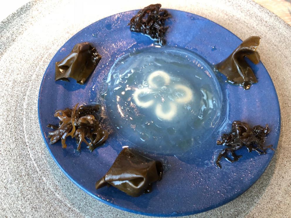 Photogallery






Noma 2.0 is in Christianshavn, the same neighbourhood as the first Noma. They’re 1.5 km apart, a 15 minutes’ walk. This picture shows the distance: to the right, there’s the warehouse of the old location (in Strandgade 93), to the left the smokestacks of Amager Bakke, the futuristic incinerator below which stands the new Noma (in Refshalevej 96)









Weather permitting, you can have a peaceful walk between the previous Noma to today’s Noma 









The new Noma is on an isthmus surrounded by canals. In the future they also want to reclaim some small parts for hydroponic farming









Bucolic scene with incinerator









Bikes left outside Noma. It’s the favourite means of transport among employees and interns









The long path taking you to the restaurant. The fence on the left shows how works are still in progress









On the two sides of the path there are the two new sections of the "Noma village", each with its specialty: grill, hot dishes, snacks, fermentations... In one month’s time, behind the fence we’ll have greenhouses, the test kitchen and the bread making area









To the left, before arriving at the restaurant, the future test kitchen. This will be run by Danish Mette Søberg with Riccardo Canella. "My first challenge?", reveals the latter, for a long time sous chef here, "is to work on the extraction of essential oils" 









The future Test Kitchen









The temporary gangway to the restaurant









Looking from the door to the restaurant, there’s a lake and the smokestacks puffing vapour from the Amager Bakke incinerator. It’s a futuristic project, both in terms of sustainability and architecture. It’s also known as Amager Slope or Copenhill, and its author is starchitect Bjarke Ingels, the same who designed the new Noma. Gradually opened in 2017, it transforms waste into electricity. The goal is to donate electricity to 62500 houses and hot water to 160000. It’s part of an ambitious project to transform Copenhagen into the first city in the world in terms of zero carbon dioxide emissions by 2025. By autumn this year, Amager Slope should open its ski slope, a climbing wall and a hiking track. You’ll be able to slalom on top of the incinerator









The windows from the dining room









Work is still in progress (photo taken on Thursday 22nd February 2018)









Traces of the old building, with barbwire. During WWII, they built bombs here









A view of the dining room at night (photo from Instagram/James Spreadbury)









The entrance to the restaurant









The usual ritual: a welcome from the entire staff, led by Rene Redzepi 









Behind the entrance, there are formaldehyde tanks with creatures from the abyss, shaped as in Damien Hirst’s works. The first image once you’re inside is to reproduce a Scandinavian village









The service kitchen is larger, more spacious and a completely open view from the dining room: "It’s the heart of our Scandinavian village", says Canella. There are 30 cooks working here now. 10 more, compared to the previous Noma









Large skylights above the cooks









There are currently more than 100 people working at Noma, of whom 63 are cooks - 26 employed, and 37 as interns









There’s fire in the kitchen, for the first time









On average, the dining room can host 40 people. "However", complains Redzepi, "there’s always someone who turns up with more people than the ones booked"









While the dining room is set, the outside space still need to be defined









The staff made the dining room decorations. There are no overly expensive designer objects









Dried fish









Seaweeds hanging from the ceiling









Dried octopus heads preserved in salt (with a balloon inside)














Bjarke Ingels and Redzepi’s plan included the wish to recreate a Danish farm









The luminous private dining room









The counter in the dining room. They drew the beams from the canals around the restaurant














The mise en place, bare and strictly without tablecloths









Water jug, candle, flower vase









A warm cloth, to begin with









Australian James Spreadbury, restaurant manager and partner at Noma









Welcome drink: Champagne extra brut Blanc d'Argile from Domaine Vouette et Sorbée









Sea Snail broth. The welcome dish at Noma is, as usual, a hot “soup”









Stefano Ferrano, from Torino, presents the following dish. There’s always a large Italian colony at Noma









Venus clams. Molluscs from Limfjord (Denmark) mixed with decorative clams, typical of Noma. Beside them, shells with blackcurrant oil and “Danish curry”, made with toasted coriander seeds, fennel and fennel seeds









The lid above the following dish. The mussels are not edible









Best of the mussel. Mussels open in a pan with water of fermented barley. «We recreate the mussel», says Canella, «using just the flaps, the best part». The paste is made with scraps from the mussel, cooked in smoked butter









The next dish is conceived and served by Riccardo Canella, the Paduan sous chef who conquered Redzepi, here with dining room intern Feline Hansen









Dried fruits and shrimps. In this case, the heads are not a decoration, but you must suck them –best not eat them because of the bones: they’re filled with a lovely prawn cream. The small crustaceans are still alive when they arrive on a ship straight from the Norwegian fjords









Inside, under the prawn broth skin, there’s fruits and vegetable preserved from the previous summer with raw prawns and gooseberry sauce with blackcurrant oil









How about beverages? There are three options, as usual: wine pairing (6 glasses plus a beer plus sake, 150 euros), juice pairing (juices and extracts, 110 euros) or a choice from the list. They recommend Champagne Chut... Libre from Val'Frison pour Dominique Derain, 50% Pinot Noir, 50% Chardonnay created by a couple who met at the old Noma. Well bodied, it will be a good match throughout the meal









As usual, the wine list starts with Champagne: the cheapest is 1400 crowns (190 euros)









White wines begin with labels from cold climates: first Austria, increasingly popular for its natural wines, then Germany, then all the others









How about Italy? Few names, among the white wines, from North and South









A dozen red/orange wines









Sea star, that is to say Cured trout roe and eggs, the emblem dish of this new era. They recommend moving the teaspoon from the heart to the edges of the tentacles. Aesthetics win over taste






