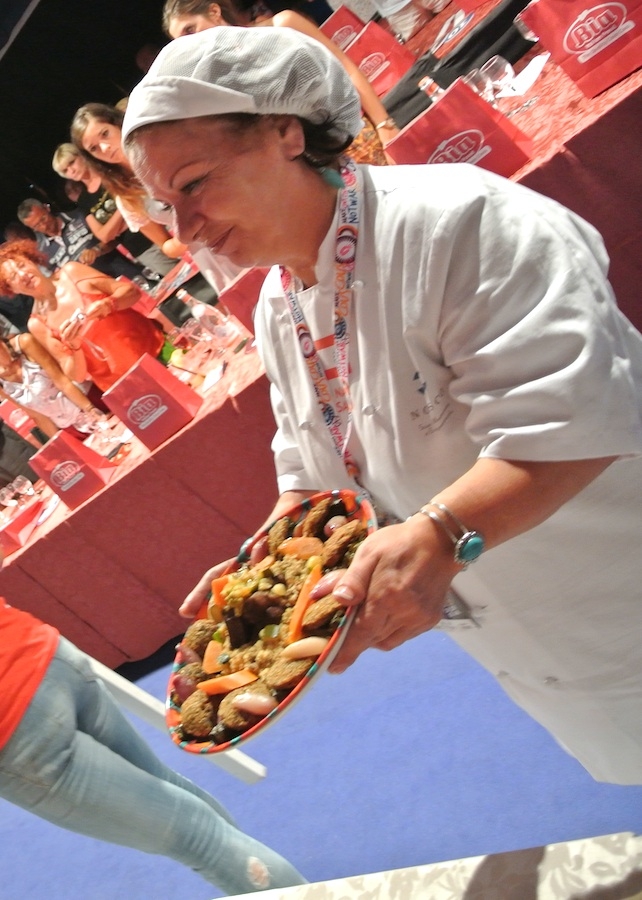 Galleria fotograficaIl cannolo di cous cous di Enrico Panero, del ristorante Da Vinci a Eataly Firenze, usato come evidenziatorePrima nazione in gara al Cous Cous Fest 2014 il Marocco con Majda Nabaoui, cuoca 19enne in forza all'Osteria Francescana a ModenaMajda Nabaoui, in Italia, a Modena, dall'et&agrave; di 9 anni, ha chiamato la sua proposta Da Modena al Marocco passando per la Sicilia, la sua colazione la mattina di sabatoI due concorrenti della Tunisia, entrambi in forza al Taglio a Milano, a destra Domenico della Salandra e al centro Mohamed Mabrouk catturato dalla bellezza della presentatrice Eliana ChiavettaL'Arancino di cous cous grazie al quale la Tunisia &egrave; arrivata alla finale a livello di giuria popolare superando il Marocco per appena un centesimo: 8,92 contro 8,91. Al suo interno scampi freschi. Nota curiosa: visto che eravano nel Trapanese, quindi Sicilia occidentale, sarebbe stato pi&ugrave; corretto chiamare il piatto ArancinaTre giorni di assaggi, tutto nel PalaBia, il tendone ridosso della spiaggia di San Vito Lo Capo. Il cielo ti invitava a mollare tutto e a tuffartiIl Cous Cous dolce, nome concreto del piatto della Francia, delle cuoche Marion Roger (cous chef di Alice Delcourt all'Erba Brusca a Milano) e Chiara Cilio, che hanno proposto un uso insolito del cous cous, in forma dolce, con tanto di gelato alla verbena. Con questo dessert, la Roger ha vinto il premio per l'originalit&agrave; e sfiorato il successo assoluto, centrato dalla Delcourt nel 2011 e 2012Maziar Farivar, radici iraniane e cittadinanza statunitense. Del suo piatto ricorderemo solo un eccessivo e gratuito uso del peperoncino. Doveva essere un cous cous nel segno dello Shrimp Jambalya ma, eliminato il prosciutto affumicato nel timore di imbattersi in musulmani in giuria, tutto &egrave; crollato.Il cous cous americano, un piatto imbarazzante, facile preferirgli quello francese. La giuria popolare ha votato il dessert 8,86 e il cous cous patriottico 7,86 (ma la giuria di esperti &egrave; stata ancora pi&ugrave; severa)Mohamed Mabrouk e Domenico della Salandra per una volta schierati nella giuria popolareIsraele in gara contro il Libano grazie a Michael Korenman, tutti presi in contropiede perch&eacute; si aspettavano un Michele, un lui e non una leiMichael Korenman &egrave; stata anche la cuica personale di Oprah Winfrey in America, conduttrice tiv&ugrave; e attrice. Il suo cous cous &egrave; piaciuto pi&ugrave; agli esperti che al pubblico. Ricco di spunti come i falafel, ottimi i singoli pezzi meno l'assemblaggio finale e un attimo inutile il tonno come nota del mare. Il piatto non aveva un nome: "Abbiamo avuto un'estata difficile per via della guerra che proprio non avevo pensato a come chiamarlo. Lo faccio ora e lo chiamo PACE". Applausi scroscianti
