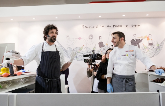 Galleria fotograficaLo stand di Acqua Panna e S.Pellegrino a Identit&agrave; Milano 2013Nello stand, l'illustrazione di Gianluca Biscalchin con le coppie protagoniste degli incontri organizzati alla tavola di Acqua Panna e S.Pellegrino durante il congressoCristina Bowerman, chef patron del Glass Hostaria e Romeo a Roma, era in coppia con Diego Confalonieri, campione di scherma nella specialit&agrave; spada - bronzo nella spada a squadre a Pechino
&nbsp;Diego Confalonieri e Cristina Bowerman all'opera allo standIl pubblico di Identit&agrave; Milano 2013 assiste all'incontro tra sport e cucinaDiego Confalonieri La seconda coppia: Lorenzo Cogo, chef patron del ristorante El Coq a Marano Vicentino, e Roy Paci, trombettista, compositore e &ldquo;gastrofonico&rdquo;
&nbsp;Nel duetto musica-cucina, Lorenzo Cogo prepara il suo piatto.....mentre Roy Paci suonaL'illustrazione di Biscalchin riprodotta nelle tovagliette dello stand