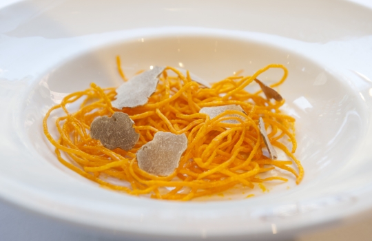 Galleria fotografica






Ravioli di latte di capra con funghi porcini alle erbe (1997)
La madre di tutte le paste ripiene craccobaronettiane.  Genesi 1997, in pieno fermento creativo alle Clivie. "E' il primo esempio di raviolo a bottone - rammenta Baronetto - Ricordo che andavo nel weekend a Giaveno, armato di tanica di plastica a comprare il latte di capra da un piccolo produttore. La cagliata era la farcia del raviolo: a contatto col caldo della cottura il ripieno si liquefaceva». Pasta ripiena d’estro ante-litteram. Un primo tornato in carta spesso negli anni milanesi. Prossimamente con asparagi verdi e tartufo nero (foto Italy behind the obvious)








Spaghetti fritti con composta di pomodoro e basilico fritto (2002)
Gli spaghetti sono cotti normalmente e poi fritti. Interessante la composta di pomodoro impigliata: si ottiene cucinando le solanacee interee in forno, su un letto di sale. Una volta scolate, ne rimane solo la polpa, un concentrato di gusto che poi si trita, condisce e incastra tra i rami di grano duro e il basilico fritto (Foto Bob Noto)








Rigatoni fritti, crema di broccolo e cozze (2003)
Anche qui, la pasta è cotta e poi fritta per un paio di minuti in padella, "come fosse una patatina". Troviamo così per la prima volta i rigatoni, un formato molto apprezzato da C&B: "E' per l'aria, per la cavità che racchiudono: sono belli e intrappolano il condimento, come dei mini-cannelloni" (Foto Bob Noto)








Garganelli d'uovo marinato alla amatriciana (2004)
I Garganelli al ragù sono la prima declinazione della tecnica dell'uovo marinato su un primo piatto: la denaturazione delle proteine del tuorlo, marinato nel sale e nello zucchero, origina una consistenza solida. E' l'affermazione dell'uovo come icona della cucina di Cracco. Dal 2004, la tecnica incontrerà numerose applicazioni ed evoluzioni: vedi il piatto in foto, oppure i celebri Spaghetti d’uovo marinato, ricci di mare e caffè (2009). E un terzo esempio ancora più recente alla fine di questa stessa gallery (foto Made in Photos)








Paccheri di gruyère (2004)
Un esempio di pasta non-pasta, un filone che negli anni ha coinvolto diversi cuochi (poco, a dire il vero, C&B). "Pasta non-pasta" perché, in questo caso, i paccheri non sono di grano duro ma di gruyère, formaggio svizzero. Il "pacchero" è servito su un'insalata. E' un piatto d'intermezzo, non confinabile al regno dei primi (Foto Bob Noto)








Tagliatelle di patate, alici e broccoli (2004)
Le tagliatelle sono in realtà gnocchi dalla forma allungata. Sono lasciate asciugare in cella e cotte normalmente. Il gusto è più dominante di quello di una tagliatela all'uovo. In stagione, ben accette le lamelle di tartufo (Foto Bob Noto)








Ravioli ripieni di maionese con ricci di mare e semi di basilico (2006) 
Evoluzione del piatto partorito alle Clivie (1997), non è un raviolo ma un bottone. E' fondato sul concetto di sottrarre pasta, il bordo del raviolo che comunemente eccede. E il condimento diventa contenuto, altro topos del procedere craccobaronettiano. In questo caso, la maionese è appena intiepidita (ma non si scioglie) ed esprime tutta la sua godibile grassezza e condimento (Foto Bob Noto)








Ravioli di broccoletti cotti sul rosmarino, semi di basilico e frutti di mare (2008) 
Un raviolo ottenuto con una tecnica interessante perché è cotto per affumicatura sul rosmarino. E così anche i frutti di mare, che cuociono per calore indiretto (foto Paolo Marchi)








Rigatoni, lattuga alla liquirizia e burro all'olio grattugiato (2009) 
Il burro all'olio è un altro importante capitolo della saga, aperto con l'ultima edizione de Lo Mejor de La Gastronomia ospitata a San Sebastian (ora è Alicante): Matteo Baronetto vinse il concorso internazionale dedicato all'extravergine di oliva con una Crema bruciata all'olio di vaniglia, seppia e garusoli. La vera novità è in quell 'burro all'olio', burro di cacao e olio crudo raffreddato, in questo caso grattuggiato sopra a rigatoni freddi, in una sorta di insalata di pasta con condimento semisolido e lattuga impanata nella polvere di liquirizia. Un altro scintillante antipasto/intermezzo (foto Brambilla/Serrani)








Timballo del Gattopardo (2009)
"Va bene l'uovo marinato e tutto il resto: ma perchè non provate a cimentarvi col Timballo di Maccheroni del Gattopardo? Quella sì è una ricetta coi contro*****", provocò il cliente gourmet. Non dirglielo due volte a C&B che son già lì a studiare e provare. Il risultato è in questo magnifico timballo che, più che sottrarre, stipa: rigatoni cotti, salsa al pomodoro, piselli, prosciutto, funghi secchi, rigaglie di pollo e coniglio... "cintare e tappare di pasta frolla tutto questo era già indice di grande creatività", commenta Baronetto, "del resto i Siciliani, già nel Seicento cucinavano l'anguilla con il coniglio"  (foto Altissimo Ceto)








Ravioli vegetali in pasta di riso su brodo di patate arrrostite (2010) 
Altri ravioli fatti a bottone, sono figli della fascinazione per la pasta di riso per celiaci di cui iniziano ad abbondare i supermercati: "Perché non utilizzarla come una pasta fresca qualsiasi? Ci siamo chiesti", racconta Baronetto, "il problema è però legato alla tenacia; è un prodotto facile a disfarsi, a meno che non la leghi con un po' di albume e latte" (della stessa famiglia, sono finiti in carta anche i Tagliolini di riso con caviale in insalata). E il brodo? E' un'infusione di patate arrostite crude su piastra (foto Arthur Angry)








Rigatoni con mastica e funghi porcini crudi (2011)
Altro piatto di cui si è parlato molto, giocato sul balsamico che si estrae dalla resina del lentischio, è piatto dell'anno a Identità Golose 2011. Valga il giudizio di allora di Paolo Marchi: "Mi hanno fulminato per profondità primordiale di sapori, i boschi di montagna e le pinete marittime, la macchia mediterranea e il tutto legato dalla intensa masticazione che i rigatoni richiedono". Un primo assoluto" (foto Brambilla/Serrani)








Tagliolini di farina di grano arso con salsiccia cruda e salsa al rafano (2012)
I tagliolini dell'anarchia, del cuoco che si ribella agli impilamenti ordinati, allo spaghetto impiattato col compasso. Una calata brutale e arruffata con un'altra costante importante: nei piatti di pasta non è il condimento a fare la diffierenza ma l'impasto. La salsiccia di vitello cruda col rafano mi ricordava un po’ il maiale col cren. Un'evoluzione più recente aggiunge uova di ricci (foto, brutta lo so, di Zanatta)








Spaghetti al peperone rosso e acciughe salate (2012)
Altro coniglio dal cilindro recente, accosta elementi che più Piemonte non si può. Il sugo di peperoni diventa succo: "Occorre centrifugare e ridurre per tirare fuori le sfumature differenti dal peperone", spiega Baronetto, "che sembra facile ma non è: se non riduci bene, c’è il rischio che diventi amaro". L'acciuga salata è il succedaneo dal sale grosso di cottura. Ma dà anche aroma e croccantezza (foto Zanatta)





