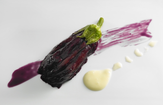 Galleria fotograficaQuello che vedete &egrave; un piatto di pura felicit&agrave;. Una sintesi suprema di minimalismo e complessit&agrave;, profondit&agrave; e nitore. Tomates en salsa, hierbas arom&aacute;ticas y fondo de alcaparras: dunque solo natura, ma che deflagra tra le fauci, assale le papille gustative e sembra lo sciabordio d&rsquo;onde contro lo scoglio, per&ograve; a percuotervi ed avvilupparvi ci pensano deliziosi umori vegetali. Vedete, si tratta di semplici pomodorini, &laquo;sono andato in un orto botanico incredibile, nel centro della Spagna. Ho assaggiato quaranta variet&agrave; di pomodori, un&rsquo;esperienza fantastica&raquo;, spiega lo chef. Al loro interno vengono siringati vari infusi a base di basilico e altre erbe, differenti l&rsquo;uno dall&rsquo;altro, il tutto si adagia su un fondo di consomm&eacute; di capperi. E&rsquo; un piatto-gioco, didascalico, splendido e spettacolare: ogni boccone rivela note diverse, qualcuno spiazza con una leggera affumicatura della polpa, ma ognuno vanta un&rsquo;incredibile potenza aromatica. &laquo;Il miglior piatto di pomodori che abbia mai mangiato&raquo;, secondo Joan Roca, tre stelle Michelin a Girona: c&rsquo;&egrave; la sorpresa delle molteplici declinazioni di sapore (&laquo;Di cosa sa questo?&raquo;, diventa una divertente caccia al gusto), s&rsquo;alternano successivi gradi di dolcezza e acidit&agrave;, fum&eacute; e speziato... E poi le consistenze, lo shot brodoso-sapido, appena tiepido, che scoppia in bocca quando il dente squarcia la tenera superficie polposa... Scoperta assoluta.L&rsquo;autore del piatto appena descritto &egrave; l&rsquo;uomo (uomo o ragazzo? In fondo &egrave; un classe 1978...) che vedete nella foto. Di lui si &egrave; detto: &laquo;Ci troviamo, lo ripetiamo per l&rsquo;ennesima volta, davanti a un GENIO. Ci&ograve; &egrave;, al disopra di qualsiasi altra considerazione, Josean Mart&iacute;nez Alija&raquo;. Ecco, condividiamo totalmente queste parole che il grande critico gastronomico spagnolo Rafael Garc&iacute;a Santos, creatore de Lo mejor de la gastronomia, rivolge nei suoi confronti. Assaggiare i piatti di Alija &egrave; un&rsquo;esperienza folgorante anche per il gourmet pi&ugrave; disincantato. Paul Bocuse: &laquo;Una delle migliori cucine della mia vita&raquo;.Alija ha da poco pi&ugrave; di tre mesi aperto il suo nuovo ristorante, Nerua, che si trova come il precedente all&rsquo;interno dell&rsquo;affascinante complesso disegnato dall&rsquo;archistar statunitense Frank O. Gehry per ospitare le collezioni del Guggenheim, a Bilbao. Lo chef &egrave; nelle cucina del museo fin dalla sua apertura, nel 1997, quando era appena maggiorenne; poco dopo primo responsabile (scelto da Martin Berasategui...). &laquo;Nerua &egrave; il culmine di tredici anni di lavoro durante i quali il ristorante del museo &egrave; stato un punto di riferimento gastronomico per i nostri visitatori. Il piacere estetico dell'edificio si sposta ora in questo nuovo spazio d&rsquo;avanguardia&raquo;, ha commentato Juan Ignacio Vidarte, direttore generale del Guggenheim. Nerua si trova accanto alla sala che ospita The Matter of Time, imponente installazione di Richard Serra, ma ha un ingresso indipendente dalla strada.Il nome Nerua &egrave; un gioco di suoni e parole. Il fiume che scorre a fianco del Guggenheim, a due passi dal ristorante, &egrave; il Nervi&oacute;n, l&rsquo;antico Nerva latino. La lingua euskadi, per&ograve;, non contempla la &ldquo;v&rdquo;, mentre quella latina classica utilizzava la &ldquo;v&rdquo; sia per indicare il relativo suono consonantico che quello vocalico &ldquo;u&rdquo;. Cos&igrave; &ldquo;Nerua&rdquo; &egrave;, nello stesso tempo, termine d&rsquo;echi prettamente baschi (l&rsquo;identit&agrave;), che designa il fiume (il territorio) e rimanda alla storia (la tradizione). Il tutto, per designare una cucina che va a braccetto col futuro.&laquo;Il peggio che pu&ograve; capitare ad un genio &egrave; di essere compreso&raquo;, ironizzava Ennio Flaiano. Su tale base non dovrebbe destar sorpresa - eppure rimaniamo ugualmente attoniti e dubbiosi - apprendere che Nerua non meriti nemmeno una stella, secondo gli immarcescibili ispettori della guida Michelin. Un altro punto di riferimento gastronomico, agli antipodi rispetto al suddetto, quello dei 50Best 2011, non colloca Alija neppure tra i primi cento chef del mondo. Perdona loro, perch&eacute; non sanno quello che fanno (Vangelo di Luca 23,34). P.s.: Identit&agrave; Golose ha premiato Alija come miglior chef straniero fin dal 2009...In una terra ad altissimo concentrato di mostri sacri, da Arzak&nbsp;(nella foto Juan Mari con la figlia Elena) a Subijana, da Aduriz al Berasategui gi&agrave; citato, Josean Mart&iacute;nez Alija - nato a L&eacute;on ma di formazione a sua volta basca - rifugge dalle influenze esterne, non si intruppa, evita i filoni consolidati cos&igrave; come quelli d&rsquo;avanguardia &agrave; la page, va dritto filato per la sua strada senza curarsi degli illustri colleghi suoi vicini. Parrebbe presunzione da enfant prodige, quale lui &egrave; stato fin dall&rsquo;inizio; invece &egrave; totale coerenza e radicalit&agrave;, persino professione d&rsquo;umilt&agrave;, perch&eacute; cos&igrave; si costringe a pedalare duro con le sole proprie gambe e a rimandare, come abbiamo visto, il tempo degli allori pi&ugrave; facili. &laquo;Il genio &egrave; nonconformismo&raquo;, Vladimir Nabokov.&nbsp;La sala del ristorante vanta un design pulito e minimalista, ad imitazione dello stile della cucina, come vedremo. Vi si accede superando l'ingresso principale che si trova vicino al fiume,&nbsp;dopo essere saliti per una scala in pietra; ci si trova nel corridoio col soffitto di titanio, nel quale una parete-cantina di vetro e metallo, trasparente, con le bottiglie in bella vista nelle intercapedini a temperatura controllata, separa dalla zona dei tavoli. Questi sono ricoperti con una tovaglia bianca, solo successivamente vi vengono via via aggiunti tutti gli altri elementi.La cucina si presenta, poco dopo l&rsquo;ingresso, sulla sinistra, completamente aperta e a vista, con spazi differenti a seconda delle temperature di lavoro. Qui Alija accoglie con gentilezza il commensale, prima che inizi la sfilata dei piatti. Tutto l'interno assume le connotazioni di uno spazio&nbsp;neutrale in cui cucina e sala da pranzo si fondono armoniosamente, l&rsquo;una estensione e &ldquo;interpretazione&rdquo; dell&rsquo;altra. Per ottenere tale fusione sono stati utilizzati gli stessi materiali e colori, legno di acero e lamina laccata. &laquo;Era ora, il momento giusto per tuffarsi in una nuova dimensione&raquo;, sussurra Josean.