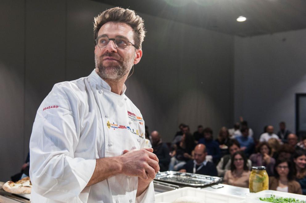 Galleria fotografica






Il Piemonte è stato punto di incontro tra il brianzolo Enrico Crippa, chef del ristorante Piazza Duomo, e il pugliese Massimiliano Prete, pizzaiolo della pizzeria Gusto Divino di Saluzzo e della Gusto Madre di Alba, città dove entrambi lavorano con molta soddisfazione da molto tempo. Una conoscenza, la loro, diventata un’amicizia e una “collaborazione” imperniata sulla stima e sul rispetto, che li ha portati a giocare con fermentazioni e lievitazioni, alta digeribilità, gusto e consistenze diverse









CosÃ¬ nasce la pizza Contaminazioni di gusto, un viaggio attraverso lâ€™Italia: su una morbida focaccia ligure al cui impasto sono state aggiunte delle cime di rapa poggia una base di 'nduja, poi un letto di burrata, una cipolla novella aperta cotta sotto vuoto che accoglie un uovo marinato al centro, completata da primule, acetosella, polvere di cime di rapa. Il tuttoÂ servito su carta da forno con accanto un brodo di cipolla per sciacquarsi la bocca.

Leggi anche:Â Le ContaminazioniÂ di Crippa e Prete, di Tania Mauri









Contaminazioni di Gusto









Si definisce lo scultore della farina Corrado Scaglione dell’Enosteria Lipen, perché la sua abilità sta nel trasformare la polvere di grano in qualcosa di concreto come una scultura, la pizza in questo caso, un disco di pasta che cresce e si trasforma.









Specializzato nella pizza napoletana «sorgente di ogni pizza che si è evoluta, una pizza dal cammino contorto perché Napoli è frutto di contaminazione di molti popoli», propone una golosa Sensazione, insieme di semplicità e territorio dato da pochi elementi, dove all’impasto partenopeo (farina, acqua, sale e lievito madre) aggiunge pomodoro del Piennolo, lardo di Arnad, mozzarella di bufala e, per completare, cipolla di Tropea fritta croccante e aneto fresco dal retrogusto amaro. Conclude, e stupisce, con un dolce di frolla con Petra 3 arricchito da una spuma di mozzarella di bufala caramellata e limone candito









Sensazione









Gennaro Nasti impara a conoscere la cucina dei grandi chef a Chicago, per poi proseguire a Parigi, patria dell’haute cuisine. Qui nel giro di qualche anno, ha aperto due locali, prima Popine e successivamente Bijou. Usa la farina Petra 9 per i suoi impasti e propone a Identità di Pizza due sue creazioni, che rimandano allo stile dei suoi locali. Nel primo prima è predominante infatti la classica pizza napoletana, nel secondo alza il livello facendosi affiancare dallo chef Marco Di Martino, ex Ducasse, per essere supportato in cucina e proporre una vera e propria pizza gourmet









Sul palco ha quindi portato altrettanti esempi delle sue pizze: la Margherita, con pomodoro stracotto come il vero il ragù napoletano, e poi la pizza Da Napoli a Parigi, dove la tradizione francese incontra quella partenopea: il topping è composto da mousse di foie gras speziato, burrata, patè di olive caiatine e un olio aromatizzato al limone per sgrassare









Da Napoli a Parigi









Mangiare e stare bene, nutrire e godere. Questi i punti di forza di Riccardo Antoniolo (nella foto, con Francesca Romana Barberini, che ha presentato le lezioni) della pizzeria Ottocento Simply Food di Bassano del Grappa, dove propone impasti di Petra tipo 2 e germinati, ricchi di fibra. Pizze buone e belle, “che funzionino”, come il finger food di pizza, “pizza in punta di dita”, vegetale ed equilibrata: la pasta viene messa all’interno di un anello di metallo per 4 ore a temperatura controllata, rovesciata e cotta nel forno, abbattuta e coppata









Su questa base aggiunge, con un sac a poche, una vellutata di rapa rossa e topinambur, che contiene molto ferro, quindi hummus di ceci, rapa fermentata, scorza di limone pastorizzata e noce pecan. Sulla seconda pizza propone un impasto 100% di farro monococco, ricco di carotene, su cui pone una purea di broccolo di Bassano, fiori di broccolo bianco appena scottato, un filetto di trota marinato in sale e zucchero di cocco per 36 ore, semi di lino spezzati, olio e pepe.

Leggi anche: Buono e sano: la lezione di Antoniolo, di Carlo Passera









Mini-pizze con vellutata di rapa rossa, topinambur, hummus di ceci, rapa fermentata, scorza di limone pastorizzata e noce pecan









Un viaggio nel tempo e nel territorio quello di Giorgio Caruso, giovane patron della pizzeria Lievità di Milano. Propone due pizze tradizionali napoletane in chiave gourmet che raccontano, con pochi e semplici ingredienti, la sua storia: la prima richiama chiaramente le origini campane del pizzaiolo, con un impasto “chiaro”, con farina Petra 1, dal cornicione pronunciato e dall’abbinamento “ad effetto” con crema di cozze, filetti di pomodoro San Marzano, fiordilatte di Agerola e buccia di limone









La seconda pizza è invece uno sguardo attento e curioso verso ciò che ha scoperto in terra lombarda, dove su un impasto integrale con Petra 9 aggiunge dell’ottimo gorgonzola, radicchio croccante e una riduzione di prugna









Pizza con gorgonzola, radicchio croccante e riduzione di prugna









Ciro Salvo, figlio d’arte, patron della pizzeria 50 Kalò di Napoli, ci fa fare un viaggio nella semplicità e nelle origini della pizza proponendo le “banali” Margherita e Marinara, «pizze che rappresentano l’eccellenza italiana nel mondo e che esaltano l’impasto, apparentemente semplici ma in realtà difficili da fare buonissime»









Impasto, manualità e cottura sono le doti del pizzaiolo secondo Salvo, che incanta con i profumi e i colori delle sue pizze, morbide e mai croccanti come vuole la tradizione napoletana, ma anche con le sue parole che parlano di arte e sapere da tramandare, divulgazione del verbo e apertura a nuove vie da percorrere per avere una pizza sempre più digeribile, senza però mai stravolgere l’identità del prodotto









Marinara









Giuseppe e Simone Vesi, padre e figlio, pizzaioli alla quarta generazione, patron delle due Pizzagourmet di Napoli, propongono sul palco la loro pizza che affonda le radici nella tradizione partenopea, ma che nello stesso tempo si evolve in un cambiamento necessario per ottenere un impasto più digeribile e sano. Un nuovo impasto quindi con farina di tipo 1, molto idratato, con 48 ore di lievitazione, una biga di 18 ore e l’uso della semola rimacinata per lo “spolvero” e, successivamente, la messa in forno









Sostenitori dei prodotti Slow Food e del territorio, farciscono il disco bianco con pomodoro giallo del Vesuvio, mozzarella di bufala campana Dop e basilico. Pochi ingredienti ma di grande gusto e sapore per una pizza che prossimamente sbarcherà anche a Milano









L'altra pizza dei Vesi: Fantasia di colori e sapori









Dal gelato alla pizza il passo è breve. Lovely Fifty Fifty (ex gelateria, oggi pizzeria) è il locale di una pizzaiola dell’Oregon, Sarah Minnick, che ha scelto di lavorare solo con produttori locali biologici e, possibilmente, a chilometro zero. I contadini la consigliano al meglio sui prodotti stagionali per esaltare sapori e colori delle sue pizze (leggi il pezzo di Paolo Marchi: Alle radici della pizza della Minnick)









Una tecnica inaspettata, la sua, dove tutti gli ingredienti vengono miscelati insieme, formaggio incluso (Grana Padana e formaggi italiani e americani) in modo da avere una cottura più omogenea. Propone una pizza "al falso pesto” con un impasto di farine americane biologiche (un panetto di pasta pesa 400 grammi perché la pizza è intesa per due persone) condita con spinaci, asparagi, piselli, burro, sale ed erbe aromatiche che richiamano il colore verde e il gusto della nota salsa ligure. Molto bella da vedere ma forse lontana da ciò a cui noi siamo abituati a mangiare sulla pizza. Per questa occasione è stata assistita da un professionista d’eccezione, il maestro Franco Pepe, da poco rientrato da Portland









Pizza al falso pesto






