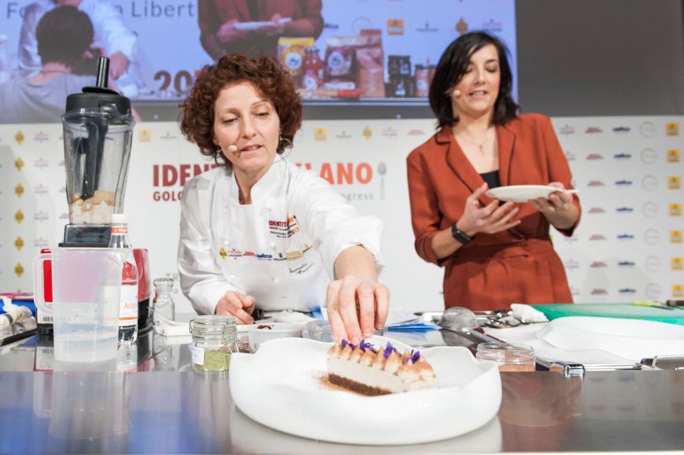 Galleria fotograficaAccompagnata sul palco dalla sorella Emanuela, Daniela Cicioni &ndash; cuoca vegana e crudista capace di trasformare radici e germogli in piatti di alta cucina &ndash; si cimenta con due sfide piuttosto ardue: prima il mondo del dolce, con un insolito tiramis&ugrave; a base di polpa di cocco, alga Irish Moss, latte di mandorle, anacardi, sciroppo d&rsquo;agave, farina di nocciole ed estratto di caff&egrave; con salsa all&rsquo;artemisia. Poi il formaggio vegano, con un erborinato a base di latte di mandorle e anacardi inoculato con il Penicillium roqueforti. Anticipazione della sua linea di formaggi di prossima uscita, accompagna gli spaghetti di konjac infusi nella tisana di fiori di pisello blu con semi di finocchio (tutte le foto sono di Brambilla-Serrani)
