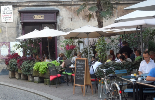Galleria fotograficaQuest&rsquo;uomo dagli occhi intelligenti e il sorriso bonario si chiama Adam Chrząstowski ed &egrave; il profeta della Nowe kuchni polskiej, la nuova cucina polacca, secondo una sua stessa definizione. Quarantatreenne di Varsavia, da quattro anni ha aperto il suo ristorante Ancora (all&rsquo;italiana, con l&rsquo;accento sulla prima &ldquo;a&rdquo;. Come a dire: di nuovo) a Cracovia, seconda citt&agrave; della Polonia, ma da sempre principale centro culturale, artistico e universitario del Paese.Krak&oacute;w &egrave; una bella citt&agrave;, con un nucleo storico (Stare Miasto) ricco di attrattive anche perch&eacute; quasi del tutto immune dalle distruzioni della seconda guerra mondiale, che hanno invece martoriato, ad esempio, Varsavia o Breslavia. Per secoli &egrave; stata residenza dei re polacchi &ndash; &egrave; tuttora Pantheon della nazione &ndash; poi terza citt&agrave; dell&rsquo;impero asburgico dopo Vienna e Budapest, sempre animata da una vivace vita commerciale, ci si trova all&rsquo;intersezione tra l&rsquo;antica via dell&rsquo;ambra, tra Carpazi e Baltico, e quella Est-Ovest che da Kiev conduce a Praga. Anche per queste molteplici influenze, dal punto di vista architettonico vanta un armonioso sovrapporsi di stili: romanico, gotico, rinascimentale (di diretta derivazione italiana, anche grazie a Bona Sforza, figlia di Gian Galeazzo, andata sposa a Sigismondo I Jagellone e dunque diventata regina), barocco... Nella foto, Rynek Głowny, ossia la pi&ugrave; grande piazza medioevale d&rsquo;Europa, cuore della citt&agrave;, con sulla sinistra la Sukiennice, gotico mercato dei tessuti, e a destra la Kości&oacute;ł Mariacki, chiesa dedicata a Maria.L&rsquo;intensit&agrave; della vita sociale cracovienne si &egrave; sempre riscontrata anche in cucina, ma i decenni sotto l&rsquo;ombrello sovietico hanno prodotto una cesura che solo ora, faticosamente, si sta cercando di ricucire. L&rsquo;isolamento &egrave; durato troppo per non pesare ancora e fa s&igrave; che in citt&agrave; furoreggino i ristoranti &ldquo;d&rsquo;importazione&rdquo; &ndash; italiani in primis &ndash; di qualit&agrave; spesso discutibile: oggi tutto ci&ograve; che &egrave; (pi&ugrave; o meno) esotico attira, dal momento che fino all&rsquo;altro ieri era vietato... L&rsquo;alta cucina &egrave; tendenzialmente d&rsquo;ispirazione francese e/o internazionale (ma senza alcun particolare acuto), mentre della tradizione polacca viene recuperata solo l&rsquo;anima popolare, non particolarmente raffinata: da qui la messe di trattorie &ldquo;tipiche&rdquo; spesso acchiappa-turisti, con menu che richiedono dosi massicce finali di Alka Seltzer. E&rsquo; un trionfo di aringhe, żurek (una zuppa d&rsquo;orzo da sempre assai utile per tamponare i sintomi post-sbornia), gołąbki (involtini di cavolo ripieni), barszcz (versione locale del borsch russo), gli onnipresenti pierogi (ravioli quadrati), per finire con gran piatti di carne arrosto, stufata, grigliata... Nella foto: spiedini, spezzatino e patate in vendita a un chiosco in centro citt&agrave;.Proprio a modificare questo andazzo punta Adam Chrząstowski col suo Ancora (nella foto). Capofila di un &ndash; ancora esiguo - gruppo di colleghi sparsi per il Paese, vuole recuperare anche la tradizione polacca nobile, nel senso letterale del termine (ci si rif&agrave; alle pietanze delle tavole aristocratiche), del tutto dimenticata sotto la cappa comunista. Dunque a Cracovia innovazione significa ora, innanzi tutto, riannodare i fili di una storia gourmand che pareva essersi persa per sempre (la Polonia, ad esempio, &egrave; leader nell&rsquo;allevamento di oche, ma poi solo il 5% di quella carne prelibata viene consumato in loco, fresco o lavorato; il mar Baltico offre a sua volta prodotti straordinari, per&ograve; gran parte del pescato finisce in Scandinavia...); in secondo luogo, significa andare alla ricerca dei tanti piccoli produttori d&rsquo;eccellenza sparsi sul grande territorio, sostenendone l&rsquo;attivit&agrave; e diffondendo una cultura slow food; infine, vuol anche dire applicare a tali materie prime e alle ricette d&rsquo;antan qualche tecnica contemporanea, stando per&ograve; attenti a non epater les bourgeois, che son di casa (la cultura borghese &egrave; storicamente cos&igrave; forte da queste parti, che la citt&agrave; risultava assai invisa ai dirigenti del defunto regime; fecero cos&igrave; costruire una sorta di Cracovia 2, ammasso periferico di acciaierie e inquinamento, proprio per innestarvi un&rsquo;anima proletaria, seppur posticcia).Non siamo quindi certamente al molecolare, l&rsquo;avanguardia &egrave; altrove: la nuova cucina polacca si sostanzia in portate che prevedono perlopi&ugrave; materie prime di qualit&agrave;, del territorio, assemblate recuperando ricette dell&rsquo;alta cucina locale (con qualche spunto creativo) ma in modo da risultare alleggerite, modernizzate e con un impiatto elegante. Per dire: la preparazione di uno simil-zabaione con frutti di bosco sostituisce al marsala un liquore polacco al miele; il (delizioso) sorbetto a met&agrave; pasto &egrave; a base di cetriolo affogato nella Zubrowka, la pregevole &ldquo;vodka all&rsquo;erba del bisonte&rdquo;, aromatizzata cio&egrave; con queste erbette brucate dagli ultimi bisonti europei che pascolano nelle lande semi-disabitate ai confini con la Bielorussia. Chrząstowski non rinuncia mai al sapore, le preparazioni sono d&rsquo;immediata soddisfazione, a rischio di perdere un poco d&rsquo;eleganza. Ma mai in piacevolezza. Menu degustazione di sette portate a 190 złoty, ossia circa 45 euro. Nella foto (invero un po&rsquo; scura, ci scuserete), il Filetto di cervo in crosta di funghi di bosco, con funghi e zucchine: carne portentosa, cotta in modo encomiabile, il miglior cervo che abbia mai mangiato.Molto buona anche la crema di gambero, con gamberetti e pane tostato al formaggio bianco. E da ricordare il piatto nella foto, una sorta di millefoglie dove strati di filetti di triglia si alternano alla pasta delle nostre chiacchiere carnascialesche (tradizione gastronomica dolce che esiste anche da queste parti), presentata in versione salata e fritta &ldquo;easy&rdquo;, il tutto a galleggiare su un mare di splendida salsa alla vaniglia e zafferano. Davvero squisito.In primo piano una zapiekanka, piatto sacro di studenti squattrinati e nottambuli d&rsquo;ogni et&agrave;. Trattasi dello street food per eccellenza di Cracovia, l&rsquo;epicentro del cui consumo &egrave; nell&rsquo;antico quartiere ebraico di Kazimierz, appena a Sud di Stare Miasto: dopo decenni di abbandono sta rinascendo, &egrave; ricco di localini ed &egrave; ora piacevole meta serale della giovent&ugrave; (autoctona o di passaggio) in cerca di divertimento. Al centro della Plac Nowy (piazza Nuova) c&rsquo;&egrave; l&rsquo;Okrqglak (la Rotonda), un edificio con tante finestre da ognuna delle quali s&rsquo;affaccia un diverso venditore di zapiekanki. E&rsquo; in sostanza una mezza baguette, tagliata per il lungo, spalmata di burro od olio e poi riccamente condita con formaggi, salumi, verdure, pat&eacute; o quant&rsquo;altro, con tocco finale di maionese, o salsa tartara, o salsa all&rsquo;aglio... Il tutto viene infine tostato al momento. Tante finestre nella Rotonda, dicevamo, ma cercate quella giusta, perch&eacute; il principe della zapiekanka &egrave; Endzior: davanti a questa gloriosa insegna noi abbiamo addentato la zapiekanka agli spinaci, che sono in crema e accompagnati da salsa tartara: gustosissima, anche se davvero inadatta a chi non ama l&rsquo;aglio. Nella foto, un altro nostro assaggio (si fa per dire: sono fette enormi!), la zapiekanka con salame e formaggio Pucok (sotto gli strati salsicciosi si nascondono anche dei funghi): una vera bomba capace di calmare i morsi della fame almeno per tre generazioni. Il tutto costa tra i 5 e i 10 złoty (ossia comunque meno di 3 euro) a seconda del condimentoAbbiamo chiesto a Chrząstowski, a termine cena: dove ci consigli di mangiare nei prossimi giorni? Lui non ama molto i colleghi di Cracovia che si siedono sugli allori (&laquo;La citt&agrave; &egrave; piena di turisti cui va benissimo gustare, finch&eacute; sono in citt&agrave;, sempre i soliti piatti. Cos&igrave; nessuno inventa, nessuno rischia...&raquo;) e ci ha dato pertanto un&rsquo;imbeccata originale: Pijalnia (nella foto). E&rsquo; la versione polacca del tapas bar spagnolo, w&oacute;dki i piva. Si trova in Tomasza 16, &egrave; aperto 24 ore su 24 e funziona cos&igrave;: si sceglie tra una breve elenco di piattini (che tanto &ldquo;ini&rdquo; non sono, anzi: con due o tre si fa cena) a 8 złoty, circa 2 euro, e li si accompagna ciascuno con una bevanda, tutte a 4 złoty, un euro (di base si dovrebbero abbinare essenzialmente shots di vodka, ma ci sono alternative meno alcoliche). Non male, oltre a essere divertente. Simile &egrave; l&rsquo;Ambasada Śledzia in Stolarskiej, proprio davanti al consolato statunitense.