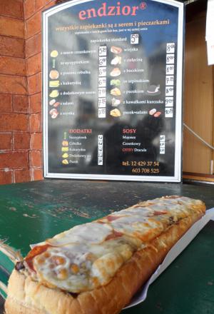 Galleria fotograficaQuest&rsquo;uomo dagli occhi intelligenti e il sorriso bonario si chiama Adam Chrząstowski ed &egrave; il profeta della Nowe kuchni polskiej, la nuova cucina polacca, secondo una sua stessa definizione. Quarantatreenne di Varsavia, da quattro anni ha aperto il suo ristorante Ancora (all&rsquo;italiana, con l&rsquo;accento sulla prima &ldquo;a&rdquo;. Come a dire: di nuovo) a Cracovia, seconda citt&agrave; della Polonia, ma da sempre principale centro culturale, artistico e universitario del Paese.Krak&oacute;w &egrave; una bella citt&agrave;, con un nucleo storico (Stare Miasto) ricco di attrattive anche perch&eacute; quasi del tutto immune dalle distruzioni della seconda guerra mondiale, che hanno invece martoriato, ad esempio, Varsavia o Breslavia. Per secoli &egrave; stata residenza dei re polacchi &ndash; &egrave; tuttora Pantheon della nazione &ndash; poi terza citt&agrave; dell&rsquo;impero asburgico dopo Vienna e Budapest, sempre animata da una vivace vita commerciale, ci si trova all&rsquo;intersezione tra l&rsquo;antica via dell&rsquo;ambra, tra Carpazi e Baltico, e quella Est-Ovest che da Kiev conduce a Praga. Anche per queste molteplici influenze, dal punto di vista architettonico vanta un armonioso sovrapporsi di stili: romanico, gotico, rinascimentale (di diretta derivazione italiana, anche grazie a Bona Sforza, figlia di Gian Galeazzo, andata sposa a Sigismondo I Jagellone e dunque diventata regina), barocco... Nella foto, Rynek Głowny, ossia la pi&ugrave; grande piazza medioevale d&rsquo;Europa, cuore della citt&agrave;, con sulla sinistra la Sukiennice, gotico mercato dei tessuti, e a destra la Kości&oacute;ł Mariacki, chiesa dedicata a Maria.L&rsquo;intensit&agrave; della vita sociale cracovienne si &egrave; sempre riscontrata anche in cucina, ma i decenni sotto l&rsquo;ombrello sovietico hanno prodotto una cesura che solo ora, faticosamente, si sta cercando di ricucire. L&rsquo;isolamento &egrave; durato troppo per non pesare ancora e fa s&igrave; che in citt&agrave; furoreggino i ristoranti &ldquo;d&rsquo;importazione&rdquo; &ndash; italiani in primis &ndash; di qualit&agrave; spesso discutibile: oggi tutto ci&ograve; che &egrave; (pi&ugrave; o meno) esotico attira, dal momento che fino all&rsquo;altro ieri era vietato... L&rsquo;alta cucina &egrave; tendenzialmente d&rsquo;ispirazione francese e/o internazionale (ma senza alcun particolare acuto), mentre della tradizione polacca viene recuperata solo l&rsquo;anima popolare, non particolarmente raffinata: da qui la messe di trattorie &ldquo;tipiche&rdquo; spesso acchiappa-turisti, con menu che richiedono dosi massicce finali di Alka Seltzer. E&rsquo; un trionfo di aringhe, żurek (una zuppa d&rsquo;orzo da sempre assai utile per tamponare i sintomi post-sbornia), gołąbki (involtini di cavolo ripieni), barszcz (versione locale del borsch russo), gli onnipresenti pierogi (ravioli quadrati), per finire con gran piatti di carne arrosto, stufata, grigliata... Nella foto: spiedini, spezzatino e patate in vendita a un chiosco in centro citt&agrave;.Proprio a modificare questo andazzo punta Adam Chrząstowski col suo Ancora (nella foto). Capofila di un &ndash; ancora esiguo - gruppo di colleghi sparsi per il Paese, vuole recuperare anche la tradizione polacca nobile, nel senso letterale del termine (ci si rif&agrave; alle pietanze delle tavole aristocratiche), del tutto dimenticata sotto la cappa comunista. Dunque a Cracovia innovazione significa ora, innanzi tutto, riannodare i fili di una storia gourmand che pareva essersi persa per sempre (la Polonia, ad esempio, &egrave; leader nell&rsquo;allevamento di oche, ma poi solo il 5% di quella carne prelibata viene consumato in loco, fresco o lavorato; il mar Baltico offre a sua volta prodotti straordinari, per&ograve; gran parte del pescato finisce in Scandinavia...); in secondo luogo, significa andare alla ricerca dei tanti piccoli produttori d&rsquo;eccellenza sparsi sul grande territorio, sostenendone l&rsquo;attivit&agrave; e diffondendo una cultura slow food; infine, vuol anche dire applicare a tali materie prime e alle ricette d&rsquo;antan qualche tecnica contemporanea, stando per&ograve; attenti a non epater les bourgeois, che son di casa (la cultura borghese &egrave; storicamente cos&igrave; forte da queste parti, che la citt&agrave; risultava assai invisa ai dirigenti del defunto regime; fecero cos&igrave; costruire una sorta di Cracovia 2, ammasso periferico di acciaierie e inquinamento, proprio per innestarvi un&rsquo;anima proletaria, seppur posticcia).Non siamo quindi certamente al molecolare, l&rsquo;avanguardia &egrave; altrove: la nuova cucina polacca si sostanzia in portate che prevedono perlopi&ugrave; materie prime di qualit&agrave;, del territorio, assemblate recuperando ricette dell&rsquo;alta cucina locale (con qualche spunto creativo) ma in modo da risultare alleggerite, modernizzate e con un impiatto elegante. Per dire: la preparazione di uno simil-zabaione con frutti di bosco sostituisce al marsala un liquore polacco al miele; il (delizioso) sorbetto a met&agrave; pasto &egrave; a base di cetriolo affogato nella Zubrowka, la pregevole &ldquo;vodka all&rsquo;erba del bisonte&rdquo;, aromatizzata cio&egrave; con queste erbette brucate dagli ultimi bisonti europei che pascolano nelle lande semi-disabitate ai confini con la Bielorussia. Chrząstowski non rinuncia mai al sapore, le preparazioni sono d&rsquo;immediata soddisfazione, a rischio di perdere un poco d&rsquo;eleganza. Ma mai in piacevolezza. Menu degustazione di sette portate a 190 złoty, ossia circa 45 euro. Nella foto (invero un po&rsquo; scura, ci scuserete), il Filetto di cervo in crosta di funghi di bosco, con funghi e zucchine: carne portentosa, cotta in modo encomiabile, il miglior cervo che abbia mai mangiato.Molto buona anche la crema di gambero, con gamberetti e pane tostato al formaggio bianco. E da ricordare il piatto nella foto, una sorta di millefoglie dove strati di filetti di triglia si alternano alla pasta delle nostre chiacchiere carnascialesche (tradizione gastronomica dolce che esiste anche da queste parti), presentata in versione salata e fritta &ldquo;easy&rdquo;, il tutto a galleggiare su un mare di splendida salsa alla vaniglia e zafferano. Davvero squisito.