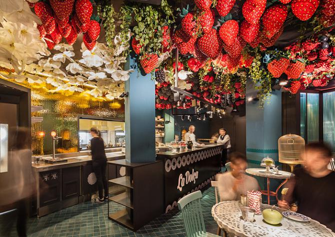 Galleria fotografica






Consommè de garbanzos. Prima che cominci il menu degustazione, viene portata al tavolo una bottiglia di vetro contenente del brodo freddo di ceci (in alto a destra). Ventitrè piatti dopo, alla fine del percorso "salato", verrà versato, in un bicchierino da grappa, del brodo caldo di jamon iberico da una teiera. Sopra ancora, la schiuma del brodo di ceci. Un caldo-freddo speciale (foto @ticketsbar instagram)









Tosta de pollo y anchoa. Primo piatto: toast di pelle di pollo con lisca di acciuga. A lato, una crema di acciughe composta da burro e pasta di acciughe









Olive Gordal. Uno dei simboli della saga Adrià: le olive sono immerse in un liquido d'olio extravergine d'oliva, cannella, buccia di limone e anice stellato. Si tirano su con un cucchiaino forato, si poggiano su una conchiglia di legno a lato e da qui in bocca. Gordal è una varietà dall'Andalusia









Prima preparazione rifinita al tavolo: Polo de almendras









Polo de almendras è uno stecco di gelato al latte di mandorle, spennellato sul posto con olio d'oliva e cosparso con granelle di mandorle, fiori di sambuco e sale. E' servito su un piatto con cubetti di ghiaccio. Dolce(salato) e gelato all'inizio del pasto e non alla fine, uno schema molto Adrià









Coliflor y caviar. Ganache di cavolfiore e caviale russo Schrenkii









Gamba a la sal fría. Gamberi marinati nel tè Lapsang Souchong con zest di bergamotto. Sono serviti su un vassoio con "neve di sale" per ricordare il ghiaccio tipico di un mercato del pesce









Atún con cerezas. Tonno e ciliegia: ventresca di tonno confit in grasso di prosciutto, accompagnata da una ciliegia affumicata (senza nocciolo)









Ceviche de melón cantaloup. Ceviche di melone cantalupo con succo di lime, coriandolo e leche de tigre di kumquat. Servito con kumquat, olio di coriandolo e neve di kumquat. Citrico alla terza









Pizza crujiente. La "pizza" di Tickets: millefoglie di regañà (torta di pane croccante di origini andaluse), stracciatella, bottarga e fichi









Porex de Calix. Marshmallow di dashi ripieno di crema acida e sormontato da caviale di Kalix, uova rosse svedesi di coregone, dalle note dolci ed eleganti









Nigiri de berenjena. Nigiri di melanzana









Cubo de wagyu. Cubo di chips di patata croccante con sopra una tartare di wagyu trattata con olio, sale, senape di Digione, uova e pepe. Una magnifica tapa da circa 2 cm per lato, che ricorda le battute al coltello della tradizione piemontese









Milhojas de atún. Millefoglie di tonno: millefoglie di patata e alga nori. In cima, tartare di tonno leggermente piccante con crema di avocado









Miniairbag de queso. Miniairbag di spuma di formaggio manchego, caviale di nocciola e polvere di buccia di nocciole









Airbaguette de rubia gallega: grissino-baguette vuoto avvolto da fettine di "prosciutto" marinato di rubia gallega, pregiata razza bovina galiziana









Encerradito de buey: involtino di ravioli di avocado con dentro granciporro con maionese di peperoncino chipotle e gelatina di coriandolo. Sotto c'è del pane sardo guttiau, sopra dei semi di chia. Un assaggio cremoso, grasso e vegetale in due bocconi magnifici









Foie y anguila. Foie gras d'anatra di Mitteault ripieno di anguilla avvolta in alga nori









Espardeña con panceta. Cetriolo di mare con la sua pelle fritta e wasabi, sopra una striscia di pancetta di prosciutto Joselito. Forse l'unico punto di domanda









Pulpo crujiente. Octopus tenero in panko (pangrattato giapponese piccante) croccante, accompagnato da cetrioli baby pickled









Cogollo con sorbete. Seconda preparazione rifnita al tavolo: cuore di lattuga accompagnato dal suo sorbetto ghiacciato con zest di rafano









Bogavante. Astice. L'unica non-tapa di tutto il percorso









Arriva il calice col Consommé freddo di ceci che rimane spumoso in cima e, sotto, il brodo caldo di jamon iberico (vedi prima slide)






