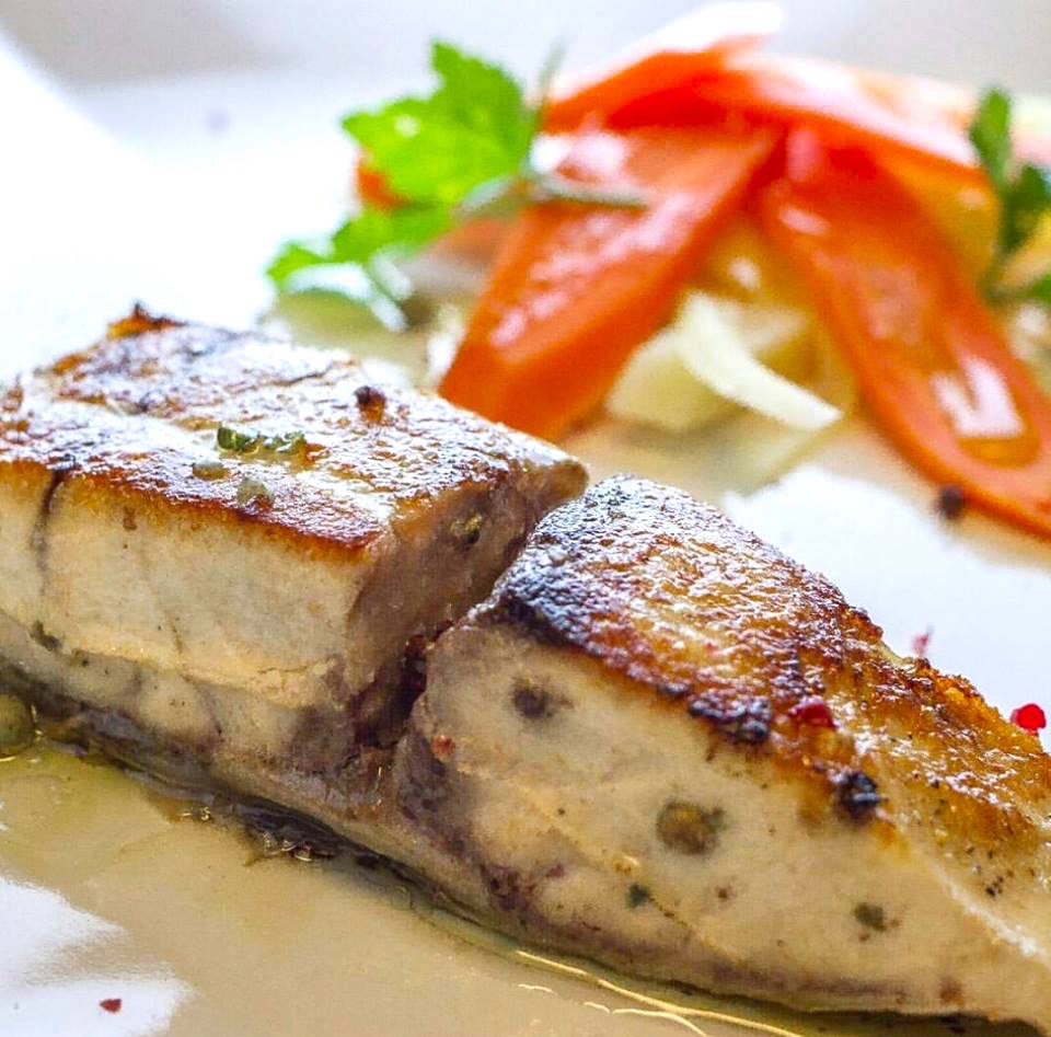 Galleria fotografica






Giuseppe Causarano, Locanda Gulfi, Chiaramonte Gulfi (Ragusa)

Palamita affumicata con foglie di vite, melagrana e azzeruole - Il piatto nasce dalle escursione sul letto del fiume Irminio, territorio sconosciuto e incontaminato che si addentra tra i Monti Iblei e sfocia a Donnalucata, dove poter raccogliere frutti, fiori e erbe selvatiche. Racconta la biodiversità di una terra fantastica come la Sicilia, lavorando uno dei pesci cosiddetti "poveri" come la palamita utilizzando dei prodotti dimenticati come le azzeruole. Il supporto del piatto disegnato da me e realizzato da un artigiano di Modica Giovanni Cerruto ricorda i ciottoli del fiume Irminio









Pino Cuttaia, La Madia, Licata (Agrigento)

Memoria visiva - E' il mio ricordo in una fetta di tonno rosso di Sicilia. Quando ero piccolo mio nonno, che era un ottimo cuoco, marinava con un po' di limone la paillard di vitello, prima di cuocerla. Faccio lo stesso col tonno, ma non lo cuocio anche se l'aspetto è simile, l'impressione della cottura è data proprio dalla marinatura. Se capita lascio che si trovi nel piatto anche il seme del limone: le mamme non si curavano mai se qualche seme cadeva nel piatto. Così presento la ricetta con una volontà evocativa di una quotidianità familiare, che è vita









Peppe Bonsignore, L’Oste e il Sacrestano, Licata (Agrigento)

Evoluzione di un'insalata di mare - Polpo cotto nel tè verde, seppia intagliata, gambero rosso di Licata il tutto servito su una crema di carote e un caramello di soia ottenuto dalla cottura dei cefalopodi. Ricordo che da bambino odiavo il polpo, fin quando mia mamma non decise di farlo con i sottaceti, dove primeggiava la carota, così iniziai ad assaggiarlo. Da quella memoria sono partito; così ho iniziato a lavorare sull'inserimento della carota. Tutto ebbe inizio nel 2009 e ogni anno modifichiamo la ricetta. Studiamo le cotture, aggiungiamo sempre qualche pesce, l’affumicatura del polpo viene fatta con ramoscelli di rosmarino secchi. La buccia di mandorla dona quel profumo di forno a legna che rievoca le nonne. Insomma oggi, nel 2016, dopo 7 anni, non diciamo mai che è una preparazione perfetta, perché è in continua evoluzione






