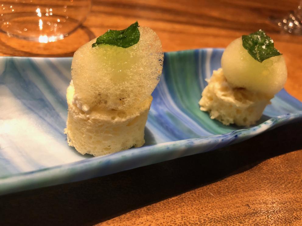 Photogallery






The sign appearing on Soi Langsuan in Bangkok, the little road where you can find restaurant Gaggan and, in front of it, the new-born Gaa, same ownership









The entrance to the restaurant, which recently got the second Michelin star. It’s open only in the evening. There are 65 people here who serve 100 clients daily, divided into two shifts (photo from themalaymailonline.com)









Gaggan’s famous emoji menu: "We first create the dish, then we sum it up with an emoji", he points out (photo from Andershusa/Instagram)









1 
Pink elderflower and watermelon
The tasting menu starts with the notes of the Foo Fighters. The entire first part of the menu is to be eaten with your hands: "This is how it works in India", he explains. First dish: a pearl among elderberry flowers and watermelon in an edible oyster shell. A debut to rinse the palate









2
Yogurt Explosion
Gaggan’s most famous dish. It’s the result of his early internship at elBulli in Roses, Catalonia. "If Ferran Adrià has had Spanish people accept a spherified olives", he says, "why shouldn’t I do the same with an emblem of India?". The spherified yogurt is made with low fat yogurt dipped in a sodium alginate









3
Lick it up. Mushroom peas
With "Lick it up", a hit from the Eighties by Kiss playing in the background, they serve this dish which you must hold with both hands and lick. The sauces, from bottom to top, in "licking order ": tomato, dehydrated mushrooms and mashed green chickpeas. On top, shaved truffle.  "Music, words, food. This is how we represent lightness"









Gaggan holds a cone









4
Tom Yum Kung
This is his version of Tom Yam (or Yum), a popular Thai soup. It’s a cold purée of tom yam served in crispy rice paper with a head of scampi to add flavour. It’s a sort of prawn cocktail in the shape of a cone









5
Goat brain, flower power
A cracker of goat brain ("to us Indians, it’s like foie gras", beams Gaggan) and rice flour. It is served to women first, playing with the similar sounds of flour and flower









6
Eggplant cookie
A cookie of aubergine, a sandwich the size of a coin, held together thanks to some onion chutney. "Out of 20, in Asia ingredients are usually worth 5, technique 15. With this dish I wanted to go in the opposite direction, return to Western minimalism with a universal emblem, that is to say aubergines. It’s a recent dish, which portraits the restaurant as it is now"









7
Chilly bon bon
Chilli pepper spheres. "Chocolates" filled with cumin, chilli pepper, ginger, and other spices. "In India there are four degrees of spiciness: hot, hotter, very hot and hell". The bon bon was mildly hot






