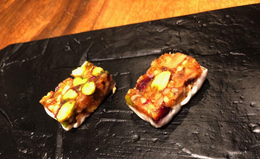 Photogallery






The sign appearing on Soi Langsuan in Bangkok, the little road where you can find restaurant Gaggan and, in front of it, the new-born Gaa, same ownership









The entrance to the restaurant, which recently got the second Michelin star. It’s open only in the evening. There are 65 people here who serve 100 clients daily, divided into two shifts (photo from themalaymailonline.com)









Gaggan’s famous emoji menu: "We first create the dish, then we sum it up with an emoji", he points out (photo from Andershusa/Instagram)









1 
Pink elderflower and watermelon
The tasting menu starts with the notes of the Foo Fighters. The entire first part of the menu is to be eaten with your hands: "This is how it works in India", he explains. First dish: a pearl among elderberry flowers and watermelon in an edible oyster shell. A debut to rinse the palate









2
Yogurt Explosion
Gaggan’s most famous dish. It’s the result of his early internship at elBulli in Roses, Catalonia. "If Ferran Adrià has had Spanish people accept a spherified olives", he says, "why shouldn’t I do the same with an emblem of India?". The spherified yogurt is made with low fat yogurt dipped in a sodium alginate









3
Lick it up. Mushroom peas
With "Lick it up", a hit from the Eighties by Kiss playing in the background, they serve this dish which you must hold with both hands and lick. The sauces, from bottom to top, in "licking order ": tomato, dehydrated mushrooms and mashed green chickpeas. On top, shaved truffle.  "Music, words, food. This is how we represent lightness"









Gaggan holds a cone









4
Tom Yum Kung
This is his version of Tom Yam (or Yum), a popular Thai soup. It’s a cold purée of tom yam served in crispy rice paper with a head of scampi to add flavour. It’s a sort of prawn cocktail in the shape of a cone









5
Goat brain, flower power
A cracker of goat brain ("to us Indians, it’s like foie gras", beams Gaggan) and rice flour. It is served to women first, playing with the similar sounds of flour and flower









6
Eggplant cookie
A cookie of aubergine, a sandwich the size of a coin, held together thanks to some onion chutney. "Out of 20, in Asia ingredients are usually worth 5, technique 15. With this dish I wanted to go in the opposite direction, return to Western minimalism with a universal emblem, that is to say aubergines. It’s a recent dish, which portraits the restaurant as it is now"









7
Chilly bon bon
Chilli pepper spheres. "Chocolates" filled with cumin, chilli pepper, ginger, and other spices. "In India there are four degrees of spiciness: hot, hotter, very hot and hell". The bon bon was mildly hot









8
Idly Sambar
Idly Sambar is a Tamil recipe, from the south of India: vegetable stew, tamarind and varying spices. "The world can be divided into two: those who eat rice, and those who eat bread. In this case, the base is bread made of fermented rice"









9
Banana chicken liver
"My daughter is one year and a half old. She’s difficult when it comes to eating. Give this combination to your children and they’ll be happy"






