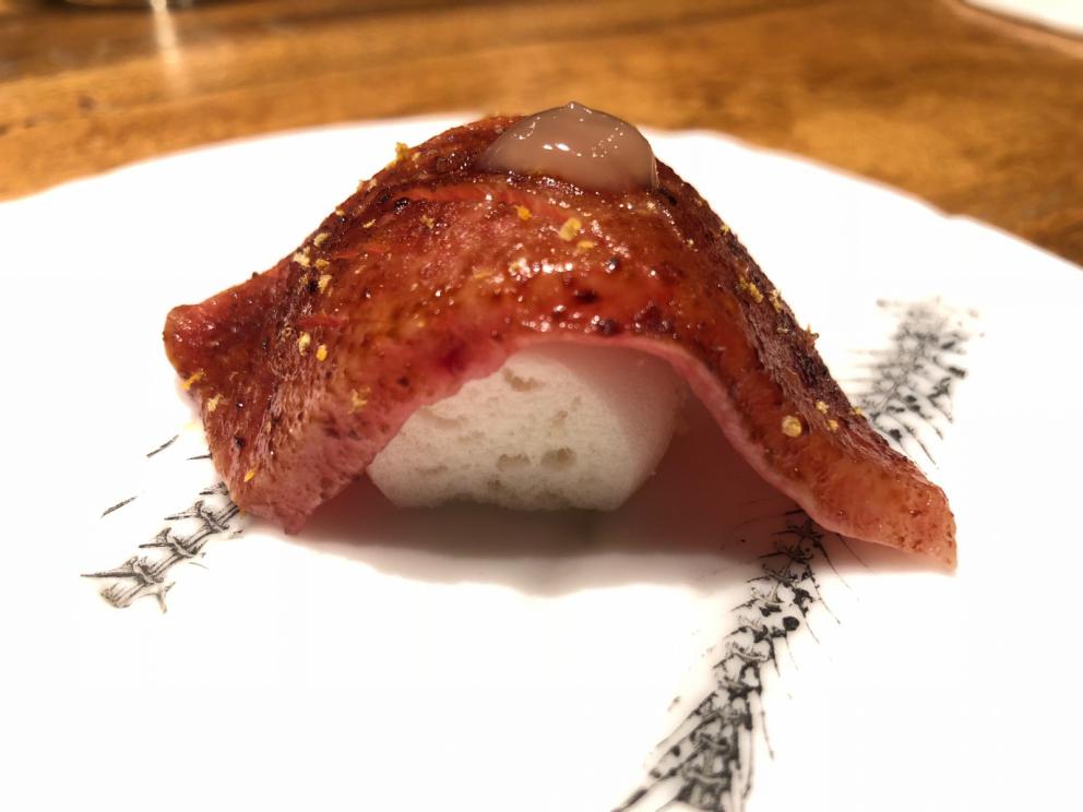 Photogallery






The sign appearing on Soi Langsuan in Bangkok, the little road where you can find restaurant Gaggan and, in front of it, the new-born Gaa, same ownership









The entrance to the restaurant, which recently got the second Michelin star. It’s open only in the evening. There are 65 people here who serve 100 clients daily, divided into two shifts (photo from themalaymailonline.com)









Gaggan’s famous emoji menu: "We first create the dish, then we sum it up with an emoji", he points out (photo from Andershusa/Instagram)









1 
Pink elderflower and watermelon
The tasting menu starts with the notes of the Foo Fighters. The entire first part of the menu is to be eaten with your hands: "This is how it works in India", he explains. First dish: a pearl among elderberry flowers and watermelon in an edible oyster shell. A debut to rinse the palate









2
Yogurt Explosion
Gaggan’s most famous dish. It’s the result of his early internship at elBulli in Roses, Catalonia. "If Ferran Adrià has had Spanish people accept a spherified olives", he says, "why shouldn’t I do the same with an emblem of India?". The spherified yogurt is made with low fat yogurt dipped in a sodium alginate









3
Lick it up. Mushroom peas
With "Lick it up", a hit from the Eighties by Kiss playing in the background, they serve this dish which you must hold with both hands and lick. The sauces, from bottom to top, in "licking order ": tomato, dehydrated mushrooms and mashed green chickpeas. On top, shaved truffle.  "Music, words, food. This is how we represent lightness"









Gaggan holds a cone









4
Tom Yum Kung
This is his version of Tom Yam (or Yum), a popular Thai soup. It’s a cold purée of tom yam served in crispy rice paper with a head of scampi to add flavour. It’s a sort of prawn cocktail in the shape of a cone









5
Goat brain, flower power
A cracker of goat brain ("to us Indians, it’s like foie gras", beams Gaggan) and rice flour. It is served to women first, playing with the similar sounds of flour and flower









6
Eggplant cookie
A cookie of aubergine, a sandwich the size of a coin, held together thanks to some onion chutney. "Out of 20, in Asia ingredients are usually worth 5, technique 15. With this dish I wanted to go in the opposite direction, return to Western minimalism with a universal emblem, that is to say aubergines. It’s a recent dish, which portraits the restaurant as it is now"









7
Chilly bon bon
Chilli pepper spheres. "Chocolates" filled with cumin, chilli pepper, ginger, and other spices. "In India there are four degrees of spiciness: hot, hotter, very hot and hell". The bon bon was mildly hot









8
Idly Sambar
Idly Sambar is a Tamil recipe, from the south of India: vegetable stew, tamarind and varying spices. "The world can be divided into two: those who eat rice, and those who eat bread. In this case, the base is bread made of fermented rice"









9
Banana chicken liver
"My daughter is one year and a half old. She’s difficult when it comes to eating. Give this combination to your children and they’ll be happy"









10
Fish Granola
Granola with fried seabass, walnuts and cheese cream









11
Gin tonic cucumber uni
Sea urchin cones, temaki, key lime and Indian tonic water. "This dish is the result of my trips to Japan: I went there 74 times only in the last couple of years. It has sea urchins from Hokkaido, in the north. In India we never eat raw food". The nori seaweed is made with dill









The selection of sea urchins from Hokkaido. "It’s worth its weight in gold", sighs Gaggan






