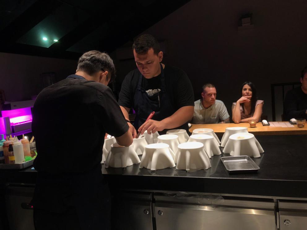 Photogallery






The sign appearing on Soi Langsuan in Bangkok, the little road where you can find restaurant Gaggan and, in front of it, the new-born Gaa, same ownership









The entrance to the restaurant, which recently got the second Michelin star. It’s open only in the evening. There are 65 people here who serve 100 clients daily, divided into two shifts (photo from themalaymailonline.com)









Gaggan’s famous emoji menu: "We first create the dish, then we sum it up with an emoji", he points out (photo from Andershusa/Instagram)









1 
Pink elderflower and watermelon
The tasting menu starts with the notes of the Foo Fighters. The entire first part of the menu is to be eaten with your hands: "This is how it works in India", he explains. First dish: a pearl among elderberry flowers and watermelon in an edible oyster shell. A debut to rinse the palate









2
Yogurt Explosion
Gaggan’s most famous dish. It’s the result of his early internship at elBulli in Roses, Catalonia. "If Ferran Adrià has had Spanish people accept a spherified olives", he says, "why shouldn’t I do the same with an emblem of India?". The spherified yogurt is made with low fat yogurt dipped in a sodium alginate









3
Lick it up. Mushroom peas
With "Lick it up", a hit from the Eighties by Kiss playing in the background, they serve this dish which you must hold with both hands and lick. The sauces, from bottom to top, in "licking order ": tomato, dehydrated mushrooms and mashed green chickpeas. On top, shaved truffle.  "Music, words, food. This is how we represent lightness"









Gaggan holds a cone









4
Tom Yum Kung
This is his version of Tom Yam (or Yum), a popular Thai soup. It’s a cold purée of tom yam served in crispy rice paper with a head of scampi to add flavour. It’s a sort of prawn cocktail in the shape of a cone









5
Goat brain, flower power
A cracker of goat brain ("to us Indians, it’s like foie gras", beams Gaggan) and rice flour. It is served to women first, playing with the similar sounds of flour and flower









6
Eggplant cookie
A cookie of aubergine, a sandwich the size of a coin, held together thanks to some onion chutney. "Out of 20, in Asia ingredients are usually worth 5, technique 15. With this dish I wanted to go in the opposite direction, return to Western minimalism with a universal emblem, that is to say aubergines. It’s a recent dish, which portraits the restaurant as it is now"









7
Chilly bon bon
Chilli pepper spheres. "Chocolates" filled with cumin, chilli pepper, ginger, and other spices. "In India there are four degrees of spiciness: hot, hotter, very hot and hell". The bon bon was mildly hot









8
Idly Sambar
Idly Sambar is a Tamil recipe, from the south of India: vegetable stew, tamarind and varying spices. "The world can be divided into two: those who eat rice, and those who eat bread. In this case, the base is bread made of fermented rice"









9
Banana chicken liver
"My daughter is one year and a half old. She’s difficult when it comes to eating. Give this combination to your children and they’ll be happy"









10
Fish Granola
Granola with fried seabass, walnuts and cheese cream









11
Gin tonic cucumber uni
Sea urchin cones, temaki, key lime and Indian tonic water. "This dish is the result of my trips to Japan: I went there 74 times only in the last couple of years. It has sea urchins from Hokkaido, in the north. In India we never eat raw food". The nori seaweed is made with dill









The selection of sea urchins from Hokkaido. "It’s worth its weight in gold", sighs Gaggan









12
Chutoro sushi
This is Gaggan’s homage to Tuna nigiri, an emblem of his future homeland (in 2021 after closing in Bangkok he’ll open a completely different restaurant in Fukuoka, Japan). Chutoro is a medium-fat tuna. In this case it is caramelised, adding a little emulsion of yuzu on top. The interesting part is below: it’s not rice, but a meringue made of all the ingredients used in sushi, that is to say vinegar, rice, sugar. "Sushi is a one way trip. You’ll never return. Nobody told me how to make it. This dish is a new take on a very personal memory"









13
Foie gras yuzu carrot
Carrot tartelette filled with foie gras. There’s no sweat on the hand: before the tasting they spray yuzu on the palm









Recipe number 14, another excursus between Japan and India









The dish is finished at the table









Whisking the mixture









14
Green vegetable matcha
Green apple gazpacho, cucumber and matcha tea. "I first fell in love with Japan thanks to tea. This looks like Japan but tastes of India and represents Gaggan"









15
Pork Vindaloo 
Vindaloo is a recipe from Goa, the Portuguese feud in west India. It’s pork, seasoned with garlic, vinegar and hot chilli pepper. In this case the fried texture is super-crispy, enriched with Japanese mustard which gives value to the Iberian pig marinated in wine and spices






