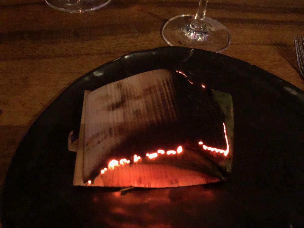 Photogallery






The sign appearing on Soi Langsuan in Bangkok, the little road where you can find restaurant Gaggan and, in front of it, the new-born Gaa, same ownership









The entrance to the restaurant, which recently got the second Michelin star. It’s open only in the evening. There are 65 people here who serve 100 clients daily, divided into two shifts (photo from themalaymailonline.com)









Gaggan’s famous emoji menu: "We first create the dish, then we sum it up with an emoji", he points out (photo from Andershusa/Instagram)









1 
Pink elderflower and watermelon
The tasting menu starts with the notes of the Foo Fighters. The entire first part of the menu is to be eaten with your hands: "This is how it works in India", he explains. First dish: a pearl among elderberry flowers and watermelon in an edible oyster shell. A debut to rinse the palate









2
Yogurt Explosion
Gaggan’s most famous dish. It’s the result of his early internship at elBulli in Roses, Catalonia. "If Ferran Adrià has had Spanish people accept a spherified olives", he says, "why shouldn’t I do the same with an emblem of India?". The spherified yogurt is made with low fat yogurt dipped in a sodium alginate









3
Lick it up. Mushroom peas
With "Lick it up", a hit from the Eighties by Kiss playing in the background, they serve this dish which you must hold with both hands and lick. The sauces, from bottom to top, in "licking order ": tomato, dehydrated mushrooms and mashed green chickpeas. On top, shaved truffle.  "Music, words, food. This is how we represent lightness"









Gaggan holds a cone









4
Tom Yum Kung
This is his version of Tom Yam (or Yum), a popular Thai soup. It’s a cold purée of tom yam served in crispy rice paper with a head of scampi to add flavour. It’s a sort of prawn cocktail in the shape of a cone









5
Goat brain, flower power
A cracker of goat brain ("to us Indians, it’s like foie gras", beams Gaggan) and rice flour. It is served to women first, playing with the similar sounds of flour and flower









6
Eggplant cookie
A cookie of aubergine, a sandwich the size of a coin, held together thanks to some onion chutney. "Out of 20, in Asia ingredients are usually worth 5, technique 15. With this dish I wanted to go in the opposite direction, return to Western minimalism with a universal emblem, that is to say aubergines. It’s a recent dish, which portraits the restaurant as it is now"









7
Chilly bon bon
Chilli pepper spheres. "Chocolates" filled with cumin, chilli pepper, ginger, and other spices. "In India there are four degrees of spiciness: hot, hotter, very hot and hell". The bon bon was mildly hot









8
Idly Sambar
Idly Sambar is a Tamil recipe, from the south of India: vegetable stew, tamarind and varying spices. "The world can be divided into two: those who eat rice, and those who eat bread. In this case, the base is bread made of fermented rice"









9
Banana chicken liver
"My daughter is one year and a half old. She’s difficult when it comes to eating. Give this combination to your children and they’ll be happy"









10
Fish Granola
Granola with fried seabass, walnuts and cheese cream









11
Gin tonic cucumber uni
Sea urchin cones, temaki, key lime and Indian tonic water. "This dish is the result of my trips to Japan: I went there 74 times only in the last couple of years. It has sea urchins from Hokkaido, in the north. In India we never eat raw food". The nori seaweed is made with dill









The selection of sea urchins from Hokkaido. "It’s worth its weight in gold", sighs Gaggan









12
Chutoro sushi
This is Gaggan’s homage to Tuna nigiri, an emblem of his future homeland (in 2021 after closing in Bangkok he’ll open a completely different restaurant in Fukuoka, Japan). Chutoro is a medium-fat tuna. In this case it is caramelised, adding a little emulsion of yuzu on top. The interesting part is below: it’s not rice, but a meringue made of all the ingredients used in sushi, that is to say vinegar, rice, sugar. "Sushi is a one way trip. You’ll never return. Nobody told me how to make it. This dish is a new take on a very personal memory"









13
Foie gras yuzu carrot
Carrot tartelette filled with foie gras. There’s no sweat on the hand: before the tasting they spray yuzu on the palm









Recipe number 14, another excursus between Japan and India









The dish is finished at the table









Whisking the mixture









14
Green vegetable matcha
Green apple gazpacho, cucumber and matcha tea. "I first fell in love with Japan thanks to tea. This looks like Japan but tastes of India and represents Gaggan"









15
Pork Vindaloo 
Vindaloo is a recipe from Goa, the Portuguese feud in west India. It’s pork, seasoned with garlic, vinegar and hot chilli pepper. In this case the fried texture is super-crispy, enriched with Japanese mustard which gives value to the Iberian pig marinated in wine and spices









New dishing out at the Chef's Table









16
Scallop uncooked curry
Scallops with green chilli, fried shallot and coconut ice cream. A “fake-curry ". The dish is served with a complaint about the past: "It’s the British who brought curry. It’s not part of our heritage, just like Chicken tikka masala. For me curry is a universal flavour, suitable for everything"









You can enrich the curry with two chilli sauces: the green, sweeter one (make love) or the red hot one (sex). "I come front the country that invented Kamasutra"









17
Sheek Kebab
A mini-sausage that’s a new take on a great Indian classic, sheek kebab. "The sausage is a clear proof of the huge influence that Chinese and Indian cuisine have had on the West. I bought this one from the market, today, and added galang and ginger. (In the photo, you can see the vegetarian version to the right)









18
Thai Green Curry
A crispy wafer made with dehydrated chicken skin with coriander sauce, in a miniaturised version of the traditional Thai green curry. In this case too, the version on the right is vegetarian









Gaggan gets a torch and starts to caramelise the banana leaves






