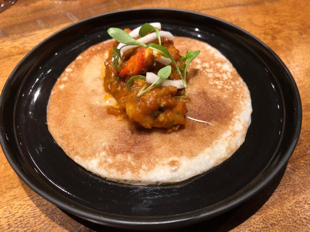 Photogallery






The sign appearing on Soi Langsuan in Bangkok, the little road where you can find restaurant Gaggan and, in front of it, the new-born Gaa, same ownership









The entrance to the restaurant, which recently got the second Michelin star. It’s open only in the evening. There are 65 people here who serve 100 clients daily, divided into two shifts (photo from themalaymailonline.com)









Gaggan’s famous emoji menu: "We first create the dish, then we sum it up with an emoji", he points out (photo from Andershusa/Instagram)









1 
Pink elderflower and watermelon
The tasting menu starts with the notes of the Foo Fighters. The entire first part of the menu is to be eaten with your hands: "This is how it works in India", he explains. First dish: a pearl among elderberry flowers and watermelon in an edible oyster shell. A debut to rinse the palate









2
Yogurt Explosion
Gaggan’s most famous dish. It’s the result of his early internship at elBulli in Roses, Catalonia. "If Ferran Adrià has had Spanish people accept a spherified olives", he says, "why shouldn’t I do the same with an emblem of India?". The spherified yogurt is made with low fat yogurt dipped in a sodium alginate









3
Lick it up. Mushroom peas
With "Lick it up", a hit from the Eighties by Kiss playing in the background, they serve this dish which you must hold with both hands and lick. The sauces, from bottom to top, in "licking order ": tomato, dehydrated mushrooms and mashed green chickpeas. On top, shaved truffle.  "Music, words, food. This is how we represent lightness"









Gaggan holds a cone









4
Tom Yum Kung
This is his version of Tom Yam (or Yum), a popular Thai soup. It’s a cold purée of tom yam served in crispy rice paper with a head of scampi to add flavour. It’s a sort of prawn cocktail in the shape of a cone









5
Goat brain, flower power
A cracker of goat brain ("to us Indians, it’s like foie gras", beams Gaggan) and rice flour. It is served to women first, playing with the similar sounds of flour and flower









6
Eggplant cookie
A cookie of aubergine, a sandwich the size of a coin, held together thanks to some onion chutney. "Out of 20, in Asia ingredients are usually worth 5, technique 15. With this dish I wanted to go in the opposite direction, return to Western minimalism with a universal emblem, that is to say aubergines. It’s a recent dish, which portraits the restaurant as it is now"









7
Chilly bon bon
Chilli pepper spheres. "Chocolates" filled with cumin, chilli pepper, ginger, and other spices. "In India there are four degrees of spiciness: hot, hotter, very hot and hell". The bon bon was mildly hot









8
Idly Sambar
Idly Sambar is a Tamil recipe, from the south of India: vegetable stew, tamarind and varying spices. "The world can be divided into two: those who eat rice, and those who eat bread. In this case, the base is bread made of fermented rice"









9
Banana chicken liver
"My daughter is one year and a half old. She’s difficult when it comes to eating. Give this combination to your children and they’ll be happy"









10
Fish Granola
Granola with fried seabass, walnuts and cheese cream









11
Gin tonic cucumber uni
Sea urchin cones, temaki, key lime and Indian tonic water. "This dish is the result of my trips to Japan: I went there 74 times only in the last couple of years. It has sea urchins from Hokkaido, in the north. In India we never eat raw food". The nori seaweed is made with dill









The selection of sea urchins from Hokkaido. "It’s worth its weight in gold", sighs Gaggan









12
Chutoro sushi
This is Gaggan’s homage to Tuna nigiri, an emblem of his future homeland (in 2021 after closing in Bangkok he’ll open a completely different restaurant in Fukuoka, Japan). Chutoro is a medium-fat tuna. In this case it is caramelised, adding a little emulsion of yuzu on top. The interesting part is below: it’s not rice, but a meringue made of all the ingredients used in sushi, that is to say vinegar, rice, sugar. "Sushi is a one way trip. You’ll never return. Nobody told me how to make it. This dish is a new take on a very personal memory"









13
Foie gras yuzu carrot
Carrot tartelette filled with foie gras. There’s no sweat on the hand: before the tasting they spray yuzu on the palm









Recipe number 14, another excursus between Japan and India









The dish is finished at the table









Whisking the mixture









14
Green vegetable matcha
Green apple gazpacho, cucumber and matcha tea. "I first fell in love with Japan thanks to tea. This looks like Japan but tastes of India and represents Gaggan"









15
Pork Vindaloo 
Vindaloo is a recipe from Goa, the Portuguese feud in west India. It’s pork, seasoned with garlic, vinegar and hot chilli pepper. In this case the fried texture is super-crispy, enriched with Japanese mustard which gives value to the Iberian pig marinated in wine and spices









New dishing out at the Chef's Table









16
Scallop uncooked curry
Scallops with green chilli, fried shallot and coconut ice cream. A “fake-curry ". The dish is served with a complaint about the past: "It’s the British who brought curry. It’s not part of our heritage, just like Chicken tikka masala. For me curry is a universal flavour, suitable for everything"









You can enrich the curry with two chilli sauces: the green, sweeter one (make love) or the red hot one (sex). "I come front the country that invented Kamasutra"









17
Sheek Kebab
A mini-sausage that’s a new take on a great Indian classic, sheek kebab. "The sausage is a clear proof of the huge influence that Chinese and Indian cuisine have had on the West. I bought this one from the market, today, and added galang and ginger. (In the photo, you can see the vegetarian version to the right)









18
Thai Green Curry
A crispy wafer made with dehydrated chicken skin with coriander sauce, in a miniaturised version of the traditional Thai green curry. In this case too, the version on the right is vegetarian









Gaggan gets a torch and starts to caramelise the banana leaves









The banana leaf is burning...









19
Seabass Bengali Mustard
...inside there’s a filet of smoked sea bass with mildly hot Bengali mustard. "It’s my oldest recipe, which is based on the ancestral gesture of man discovering fire. Before I die, I want to eat this"









20
Charcoal lotus stem
Fried aubergine with a stalk of lotus inside. It’s a total black fried snack, which looks similar to charcoal






