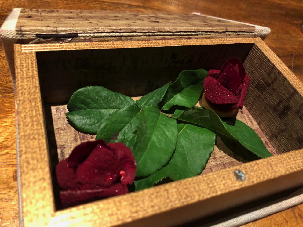 Photogallery






The sign appearing on Soi Langsuan in Bangkok, the little road where you can find restaurant Gaggan and, in front of it, the new-born Gaa, same ownership









The entrance to the restaurant, which recently got the second Michelin star. It’s open only in the evening. There are 65 people here who serve 100 clients daily, divided into two shifts (photo from themalaymailonline.com)









Gaggan’s famous emoji menu: "We first create the dish, then we sum it up with an emoji", he points out (photo from Andershusa/Instagram)









1 
Pink elderflower and watermelon
The tasting menu starts with the notes of the Foo Fighters. The entire first part of the menu is to be eaten with your hands: "This is how it works in India", he explains. First dish: a pearl among elderberry flowers and watermelon in an edible oyster shell. A debut to rinse the palate









2
Yogurt Explosion
Gaggan’s most famous dish. It’s the result of his early internship at elBulli in Roses, Catalonia. "If Ferran Adrià has had Spanish people accept a spherified olives", he says, "why shouldn’t I do the same with an emblem of India?". The spherified yogurt is made with low fat yogurt dipped in a sodium alginate









3
Lick it up. Mushroom peas
With "Lick it up", a hit from the Eighties by Kiss playing in the background, they serve this dish which you must hold with both hands and lick. The sauces, from bottom to top, in "licking order ": tomato, dehydrated mushrooms and mashed green chickpeas. On top, shaved truffle.  "Music, words, food. This is how we represent lightness"









Gaggan holds a cone









4
Tom Yum Kung
This is his version of Tom Yam (or Yum), a popular Thai soup. It’s a cold purée of tom yam served in crispy rice paper with a head of scampi to add flavour. It’s a sort of prawn cocktail in the shape of a cone









5
Goat brain, flower power
A cracker of goat brain ("to us Indians, it’s like foie gras", beams Gaggan) and rice flour. It is served to women first, playing with the similar sounds of flour and flower









6
Eggplant cookie
A cookie of aubergine, a sandwich the size of a coin, held together thanks to some onion chutney. "Out of 20, in Asia ingredients are usually worth 5, technique 15. With this dish I wanted to go in the opposite direction, return to Western minimalism with a universal emblem, that is to say aubergines. It’s a recent dish, which portraits the restaurant as it is now"









7
Chilly bon bon
Chilli pepper spheres. "Chocolates" filled with cumin, chilli pepper, ginger, and other spices. "In India there are four degrees of spiciness: hot, hotter, very hot and hell". The bon bon was mildly hot









8
Idly Sambar
Idly Sambar is a Tamil recipe, from the south of India: vegetable stew, tamarind and varying spices. "The world can be divided into two: those who eat rice, and those who eat bread. In this case, the base is bread made of fermented rice"









9
Banana chicken liver
"My daughter is one year and a half old. She’s difficult when it comes to eating. Give this combination to your children and they’ll be happy"









10
Fish Granola
Granola with fried seabass, walnuts and cheese cream









11
Gin tonic cucumber uni
Sea urchin cones, temaki, key lime and Indian tonic water. "This dish is the result of my trips to Japan: I went there 74 times only in the last couple of years. It has sea urchins from Hokkaido, in the north. In India we never eat raw food". The nori seaweed is made with dill









The selection of sea urchins from Hokkaido. "It’s worth its weight in gold", sighs Gaggan









12
Chutoro sushi
This is Gaggan’s homage to Tuna nigiri, an emblem of his future homeland (in 2021 after closing in Bangkok he’ll open a completely different restaurant in Fukuoka, Japan). Chutoro is a medium-fat tuna. In this case it is caramelised, adding a little emulsion of yuzu on top. The interesting part is below: it’s not rice, but a meringue made of all the ingredients used in sushi, that is to say vinegar, rice, sugar. "Sushi is a one way trip. You’ll never return. Nobody told me how to make it. This dish is a new take on a very personal memory"









13
Foie gras yuzu carrot
Carrot tartelette filled with foie gras. There’s no sweat on the hand: before the tasting they spray yuzu on the palm









Recipe number 14, another excursus between Japan and India









The dish is finished at the table









Whisking the mixture









14
Green vegetable matcha
Green apple gazpacho, cucumber and matcha tea. "I first fell in love with Japan thanks to tea. This looks like Japan but tastes of India and represents Gaggan"









15
Pork Vindaloo 
Vindaloo is a recipe from Goa, the Portuguese feud in west India. It’s pork, seasoned with garlic, vinegar and hot chilli pepper. In this case the fried texture is super-crispy, enriched with Japanese mustard which gives value to the Iberian pig marinated in wine and spices









New dishing out at the Chef's Table









16
Scallop uncooked curry
Scallops with green chilli, fried shallot and coconut ice cream. A “fake-curry ". The dish is served with a complaint about the past: "It’s the British who brought curry. It’s not part of our heritage, just like Chicken tikka masala. For me curry is a universal flavour, suitable for everything"









You can enrich the curry with two chilli sauces: the green, sweeter one (make love) or the red hot one (sex). "I come front the country that invented Kamasutra"









17
Sheek Kebab
A mini-sausage that’s a new take on a great Indian classic, sheek kebab. "The sausage is a clear proof of the huge influence that Chinese and Indian cuisine have had on the West. I bought this one from the market, today, and added galang and ginger. (In the photo, you can see the vegetarian version to the right)









18
Thai Green Curry
A crispy wafer made with dehydrated chicken skin with coriander sauce, in a miniaturised version of the traditional Thai green curry. In this case too, the version on the right is vegetarian









Gaggan gets a torch and starts to caramelise the banana leaves









The banana leaf is burning...









19
Seabass Bengali Mustard
...inside there’s a filet of smoked sea bass with mildly hot Bengali mustard. "It’s my oldest recipe, which is based on the ancestral gesture of man discovering fire. Before I die, I want to eat this"









20
Charcoal lotus stem
Fried aubergine with a stalk of lotus inside. It’s a total black fried snack, which looks similar to charcoal









21
Lobster dosa
Dosa (rice batter) with open lobster, in Indian sauce. You have to close it and eat it like a taco
 









The quotation of Stéphane Mallarmé






