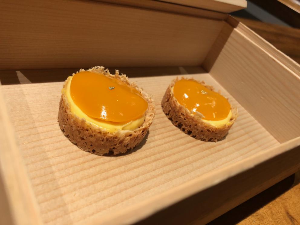 Photogallery






The sign appearing on Soi Langsuan in Bangkok, the little road where you can find restaurant Gaggan and, in front of it, the new-born Gaa, same ownership









The entrance to the restaurant, which recently got the second Michelin star. It’s open only in the evening. There are 65 people here who serve 100 clients daily, divided into two shifts (photo from themalaymailonline.com)









Gaggan’s famous emoji menu: "We first create the dish, then we sum it up with an emoji", he points out (photo from Andershusa/Instagram)









1 
Pink elderflower and watermelon
The tasting menu starts with the notes of the Foo Fighters. The entire first part of the menu is to be eaten with your hands: "This is how it works in India", he explains. First dish: a pearl among elderberry flowers and watermelon in an edible oyster shell. A debut to rinse the palate









2
Yogurt Explosion
Gaggan’s most famous dish. It’s the result of his early internship at elBulli in Roses, Catalonia. "If Ferran Adrià has had Spanish people accept a spherified olives", he says, "why shouldn’t I do the same with an emblem of India?". The spherified yogurt is made with low fat yogurt dipped in a sodium alginate









3
Lick it up. Mushroom peas
With "Lick it up", a hit from the Eighties by Kiss playing in the background, they serve this dish which you must hold with both hands and lick. The sauces, from bottom to top, in "licking order ": tomato, dehydrated mushrooms and mashed green chickpeas. On top, shaved truffle.  "Music, words, food. This is how we represent lightness"









Gaggan holds a cone









4
Tom Yum Kung
This is his version of Tom Yam (or Yum), a popular Thai soup. It’s a cold purée of tom yam served in crispy rice paper with a head of scampi to add flavour. It’s a sort of prawn cocktail in the shape of a cone









5
Goat brain, flower power
A cracker of goat brain ("to us Indians, it’s like foie gras", beams Gaggan) and rice flour. It is served to women first, playing with the similar sounds of flour and flower









6
Eggplant cookie
A cookie of aubergine, a sandwich the size of a coin, held together thanks to some onion chutney. "Out of 20, in Asia ingredients are usually worth 5, technique 15. With this dish I wanted to go in the opposite direction, return to Western minimalism with a universal emblem, that is to say aubergines. It’s a recent dish, which portraits the restaurant as it is now"









7
Chilly bon bon
Chilli pepper spheres. "Chocolates" filled with cumin, chilli pepper, ginger, and other spices. "In India there are four degrees of spiciness: hot, hotter, very hot and hell". The bon bon was mildly hot









8
Idly Sambar
Idly Sambar is a Tamil recipe, from the south of India: vegetable stew, tamarind and varying spices. "The world can be divided into two: those who eat rice, and those who eat bread. In this case, the base is bread made of fermented rice"









9
Banana chicken liver
"My daughter is one year and a half old. She’s difficult when it comes to eating. Give this combination to your children and they’ll be happy"









10
Fish Granola
Granola with fried seabass, walnuts and cheese cream









11
Gin tonic cucumber uni
Sea urchin cones, temaki, key lime and Indian tonic water. "This dish is the result of my trips to Japan: I went there 74 times only in the last couple of years. It has sea urchins from Hokkaido, in the north. In India we never eat raw food". The nori seaweed is made with dill









The selection of sea urchins from Hokkaido. "It’s worth its weight in gold", sighs Gaggan









12
Chutoro sushi
This is Gaggan’s homage to Tuna nigiri, an emblem of his future homeland (in 2021 after closing in Bangkok he’ll open a completely different restaurant in Fukuoka, Japan). Chutoro is a medium-fat tuna. In this case it is caramelised, adding a little emulsion of yuzu on top. The interesting part is below: it’s not rice, but a meringue made of all the ingredients used in sushi, that is to say vinegar, rice, sugar. "Sushi is a one way trip. You’ll never return. Nobody told me how to make it. This dish is a new take on a very personal memory"









13
Foie gras yuzu carrot
Carrot tartelette filled with foie gras. There’s no sweat on the hand: before the tasting they spray yuzu on the palm









Recipe number 14, another excursus between Japan and India









The dish is finished at the table









Whisking the mixture









14
Green vegetable matcha
Green apple gazpacho, cucumber and matcha tea. "I first fell in love with Japan thanks to tea. This looks like Japan but tastes of India and represents Gaggan"









15
Pork Vindaloo 
Vindaloo is a recipe from Goa, the Portuguese feud in west India. It’s pork, seasoned with garlic, vinegar and hot chilli pepper. In this case the fried texture is super-crispy, enriched with Japanese mustard which gives value to the Iberian pig marinated in wine and spices









New dishing out at the Chef's Table









16
Scallop uncooked curry
Scallops with green chilli, fried shallot and coconut ice cream. A “fake-curry ". The dish is served with a complaint about the past: "It’s the British who brought curry. It’s not part of our heritage, just like Chicken tikka masala. For me curry is a universal flavour, suitable for everything"









You can enrich the curry with two chilli sauces: the green, sweeter one (make love) or the red hot one (sex). "I come front the country that invented Kamasutra"









17
Sheek Kebab
A mini-sausage that’s a new take on a great Indian classic, sheek kebab. "The sausage is a clear proof of the huge influence that Chinese and Indian cuisine have had on the West. I bought this one from the market, today, and added galang and ginger. (In the photo, you can see the vegetarian version to the right)









18
Thai Green Curry
A crispy wafer made with dehydrated chicken skin with coriander sauce, in a miniaturised version of the traditional Thai green curry. In this case too, the version on the right is vegetarian









Gaggan gets a torch and starts to caramelise the banana leaves









The banana leaf is burning...









19
Seabass Bengali Mustard
...inside there’s a filet of smoked sea bass with mildly hot Bengali mustard. "It’s my oldest recipe, which is based on the ancestral gesture of man discovering fire. Before I die, I want to eat this"









20
Charcoal lotus stem
Fried aubergine with a stalk of lotus inside. It’s a total black fried snack, which looks similar to charcoal









21
Lobster dosa
Dosa (rice batter) with open lobster, in Indian sauce. You have to close it and eat it like a taco
 









The quotation of Stéphane Mallarmé









22
Beetroot rose
Beetroot rose with Tonka bean. A pre-dessert. "Kiss from a rose" by Seal starts in the background









23
Milk cake, Riesling Muscat
A dish for a toast, shaped like the traditional Chinese moon cake. It is filled with Riesling ice cream, which is rather pleasant and sour. "Milk is the most important ingredient we have. In Thailand it’s not very good but we tolerate it"









24
Lemon cheesecake
Lemon cheesecake ice cream on a stick. "Why reproduce the Minions? Because food must be fun"









Ultimo atto...






