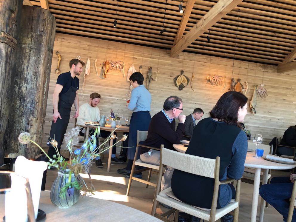 Photogallery






Noma 2.0 is in Christianshavn, the same neighbourhood as the first Noma. They’re 1.5 km apart, a 15 minutes’ walk. This picture shows the distance: to the right, there’s the warehouse of the old location (in Strandgade 93), to the left the smokestacks of Amager Bakke, the futuristic incinerator below which stands the new Noma (in Refshalevej 96)









Weather permitting, you can have a peaceful walk between the previous Noma to today’s Noma 









The new Noma is on an isthmus surrounded by canals. In the future they also want to reclaim some small parts for hydroponic farming









Bucolic scene with incinerator









Bikes left outside Noma. It’s the favourite means of transport among employees and interns









The long path taking you to the restaurant. The fence on the left shows how works are still in progress









On the two sides of the path there are the two new sections of the "Noma village", each with its specialty: grill, hot dishes, snacks, fermentations... In one month’s time, behind the fence we’ll have greenhouses, the test kitchen and the bread making area









To the left, before arriving at the restaurant, the future test kitchen. This will be run by Danish Mette Søberg with Riccardo Canella. "My first challenge?", reveals the latter, for a long time sous chef here, "is to work on the extraction of essential oils" 









The future Test Kitchen









The temporary gangway to the restaurant









Looking from the door to the restaurant, there’s a lake and the smokestacks puffing vapour from the Amager Bakke incinerator. It’s a futuristic project, both in terms of sustainability and architecture. It’s also known as Amager Slope or Copenhill, and its author is starchitect Bjarke Ingels, the same who designed the new Noma. Gradually opened in 2017, it transforms waste into electricity. The goal is to donate electricity to 62500 houses and hot water to 160000. It’s part of an ambitious project to transform Copenhagen into the first city in the world in terms of zero carbon dioxide emissions by 2025. By autumn this year, Amager Slope should open its ski slope, a climbing wall and a hiking track. You’ll be able to slalom on top of the incinerator









The windows from the dining room









Work is still in progress (photo taken on Thursday 22nd February 2018)









Traces of the old building, with barbwire. During WWII, they built bombs here









A view of the dining room at night (photo from Instagram/James Spreadbury)









The entrance to the restaurant









The usual ritual: a welcome from the entire staff, led by Rene Redzepi 









Behind the entrance, there are formaldehyde tanks with creatures from the abyss, shaped as in Damien Hirst’s works. The first image once you’re inside is to reproduce a Scandinavian village









The service kitchen is larger, more spacious and a completely open view from the dining room: "It’s the heart of our Scandinavian village", says Canella. There are 30 cooks working here now. 10 more, compared to the previous Noma









Large skylights above the cooks









There are currently more than 100 people working at Noma, of whom 63 are cooks - 26 employed, and 37 as interns









There’s fire in the kitchen, for the first time









On average, the dining room can host 40 people. "However", complains Redzepi, "there’s always someone who turns up with more people than the ones booked"









While the dining room is set, the outside space still need to be defined









The staff made the dining room decorations. There are no overly expensive designer objects









Dried fish









Seaweeds hanging from the ceiling









Dried octopus heads preserved in salt (with a balloon inside)














Bjarke Ingels and Redzepi’s plan included the wish to recreate a Danish farm









The luminous private dining room









The counter in the dining room. They drew the beams from the canals around the restaurant






