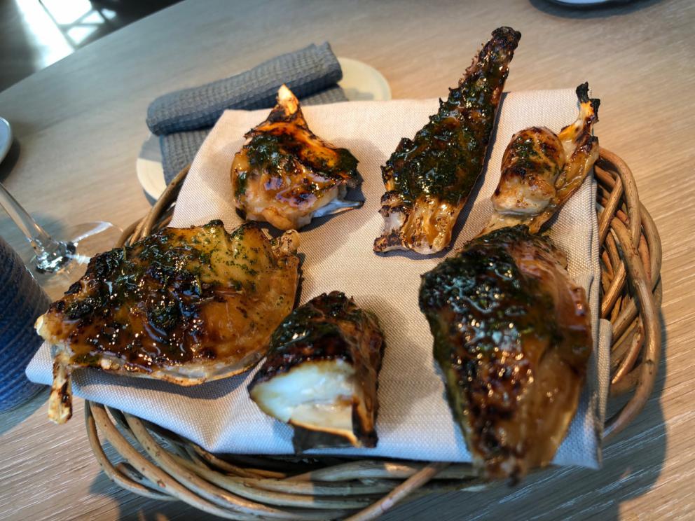 Photogallery






Noma 2.0 is in Christianshavn, the same neighbourhood as the first Noma. They’re 1.5 km apart, a 15 minutes’ walk. This picture shows the distance: to the right, there’s the warehouse of the old location (in Strandgade 93), to the left the smokestacks of Amager Bakke, the futuristic incinerator below which stands the new Noma (in Refshalevej 96)









Weather permitting, you can have a peaceful walk between the previous Noma to today’s Noma 









The new Noma is on an isthmus surrounded by canals. In the future they also want to reclaim some small parts for hydroponic farming









Bucolic scene with incinerator









Bikes left outside Noma. It’s the favourite means of transport among employees and interns









The long path taking you to the restaurant. The fence on the left shows how works are still in progress









On the two sides of the path there are the two new sections of the "Noma village", each with its specialty: grill, hot dishes, snacks, fermentations... In one month’s time, behind the fence we’ll have greenhouses, the test kitchen and the bread making area









To the left, before arriving at the restaurant, the future test kitchen. This will be run by Danish Mette Søberg with Riccardo Canella. "My first challenge?", reveals the latter, for a long time sous chef here, "is to work on the extraction of essential oils" 









The future Test Kitchen









The temporary gangway to the restaurant









Looking from the door to the restaurant, there’s a lake and the smokestacks puffing vapour from the Amager Bakke incinerator. It’s a futuristic project, both in terms of sustainability and architecture. It’s also known as Amager Slope or Copenhill, and its author is starchitect Bjarke Ingels, the same who designed the new Noma. Gradually opened in 2017, it transforms waste into electricity. The goal is to donate electricity to 62500 houses and hot water to 160000. It’s part of an ambitious project to transform Copenhagen into the first city in the world in terms of zero carbon dioxide emissions by 2025. By autumn this year, Amager Slope should open its ski slope, a climbing wall and a hiking track. You’ll be able to slalom on top of the incinerator









The windows from the dining room









Work is still in progress (photo taken on Thursday 22nd February 2018)









Traces of the old building, with barbwire. During WWII, they built bombs here









A view of the dining room at night (photo from Instagram/James Spreadbury)









The entrance to the restaurant









The usual ritual: a welcome from the entire staff, led by Rene Redzepi 









Behind the entrance, there are formaldehyde tanks with creatures from the abyss, shaped as in Damien Hirst’s works. The first image once you’re inside is to reproduce a Scandinavian village









The service kitchen is larger, more spacious and a completely open view from the dining room: "It’s the heart of our Scandinavian village", says Canella. There are 30 cooks working here now. 10 more, compared to the previous Noma









Large skylights above the cooks









There are currently more than 100 people working at Noma, of whom 63 are cooks - 26 employed, and 37 as interns









There’s fire in the kitchen, for the first time









On average, the dining room can host 40 people. "However", complains Redzepi, "there’s always someone who turns up with more people than the ones booked"









While the dining room is set, the outside space still need to be defined









The staff made the dining room decorations. There are no overly expensive designer objects









Dried fish









Seaweeds hanging from the ceiling









Dried octopus heads preserved in salt (with a balloon inside)














Bjarke Ingels and Redzepi’s plan included the wish to recreate a Danish farm









The luminous private dining room









The counter in the dining room. They drew the beams from the canals around the restaurant














The mise en place, bare and strictly without tablecloths









Water jug, candle, flower vase









A warm cloth, to begin with









Australian James Spreadbury, restaurant manager and partner at Noma









Welcome drink: Champagne extra brut Blanc d'Argile from Domaine Vouette et Sorbée









Sea Snail broth. The welcome dish at Noma is, as usual, a hot “soup”









Stefano Ferrano, from Torino, presents the following dish. There’s always a large Italian colony at Noma









Venus clams. Molluscs from Limfjord (Denmark) mixed with decorative clams, typical of Noma. Beside them, shells with blackcurrant oil and “Danish curry”, made with toasted coriander seeds, fennel and fennel seeds









The lid above the following dish. The mussels are not edible









Best of the mussel. Mussels open in a pan with water of fermented barley. «We recreate the mussel», says Canella, «using just the flaps, the best part». The paste is made with scraps from the mussel, cooked in smoked butter









The next dish is conceived and served by Riccardo Canella, the Paduan sous chef who conquered Redzepi, here with dining room intern Feline Hansen









Dried fruits and shrimps. In this case, the heads are not a decoration, but you must suck them –best not eat them because of the bones: they’re filled with a lovely prawn cream. The small crustaceans are still alive when they arrive on a ship straight from the Norwegian fjords









Inside, under the prawn broth skin, there’s fruits and vegetable preserved from the previous summer with raw prawns and gooseberry sauce with blackcurrant oil









How about beverages? There are three options, as usual: wine pairing (6 glasses plus a beer plus sake, 150 euros), juice pairing (juices and extracts, 110 euros) or a choice from the list. They recommend Champagne Chut... Libre from Val'Frison pour Dominique Derain, 50% Pinot Noir, 50% Chardonnay created by a couple who met at the old Noma. Well bodied, it will be a good match throughout the meal









As usual, the wine list starts with Champagne: the cheapest is 1400 crowns (190 euros)









White wines begin with labels from cold climates: first Austria, increasingly popular for its natural wines, then Germany, then all the others









How about Italy? Few names, among the white wines, from North and South









A dozen red/orange wines









Sea star, that is to say Cured trout roe and eggs, the emblem dish of this new era. They recommend moving the teaspoon from the heart to the edges of the tentacles. Aesthetics win over taste









Jellyfish. The jellyfish gel in the middle is in fact a clarified broth of calamari and recalls the texture of jellyfish. "We tried to cook jellyfish in 300 different ways but none was convincing so far". All around, pickled seaweed. The gel is almost tasteless, it serves to clean the palate after the pickles









Rene Redzepi himself presents the content of the first Seafood platter.









French style service with a small plate below for the empty shells









It’s made of two (per two) pieces: queen clam and mahogany clam









The Queen Clam is a very small variety of Norwegian scallop, seasoned with a vegetal reduction made with cucumber and peas miso. The red tip is the coral. "You should eat it using the top shell ", recommends Redzepi









The Mahogany clam is a centennial clam from the North Sea, very popular in Denmark and Iceland. «You can tell the age by the number of rings, like with trees», says Redzepi, «In 2007 they found one that was 450 years old. We’ve had it in the menu for a decade or so». The razor clam shell serves as teaspoon









Inside, there’s obviously not just a bare Mahogany. «We open it when the client arrives», says Canella, «remove the entrails and then slice it so as to preserve its firm texture». It’s seasoned with stir-fried gooseberry, capers of blackcurrants and blackcurrant sprouts preserved in vinegar. The sauce is made with mussel water









A note on the chairs: they’re more minimalistic. They’re no longer covered in sheepskin or leather from other Danish animals, in the style of Noma 1.0. The most significant element is the napkin: if you go to the toilet, they no longer replace it with a new one. There’s the old one, tied to the chair. "This is sustainability", they explain









The second seafood platter. It’s made of Sea cucumber and sour cream in various textures, including «chicharrones» (at 9 o’clock), sea urchins (at 12 and 3) and gigas oyster (at 6)









Sea urchins pressed in fresh cream and pumpkin seeds









Giga Oyster, a huge oyster from the Pacific, quickly steamed and garnished with pickles. Noma only reserved one thousand of these. In the menu until available









The following dish, off the menu, is again from Canella: horse mussel ragout, rare specimen of which 30 arrive at 'Noma each week









They cook the mussel as if it were kidney, in a sort of Bolognese sauce but with ginger. Ginger? "Yes, we’ve decided to include it, as with other spices, after our Mexican experience"









Another Italian presents a dish, Edoardo Fiaschi from Prato, at Noma for 3 years now









Squid in seaweed butter. An almost neglected Danish squid lightly seared in fermented koji oil, rolled and seasoned with seaweed butter and served on sticks of blackcurrant that widen its aromas. Formidable and beautiful









The following dish is inside a nice bee wax container. It’s made with balloons covered multiple times in bee wax. «We spent weeks making them. We’ve made thousands». They’re disposable...









Sea snail and roses. They recommend to: "Eat it keeping the bee wax on your hands "









Sea snail. Another small nibble from the top part of the sea snail, lightly warmed up in water and served on a reduction of lemon thyme









A sea snail toothpick, initially carved by Redzepi himself









Head of the cod, (right), the real main course at Noma






