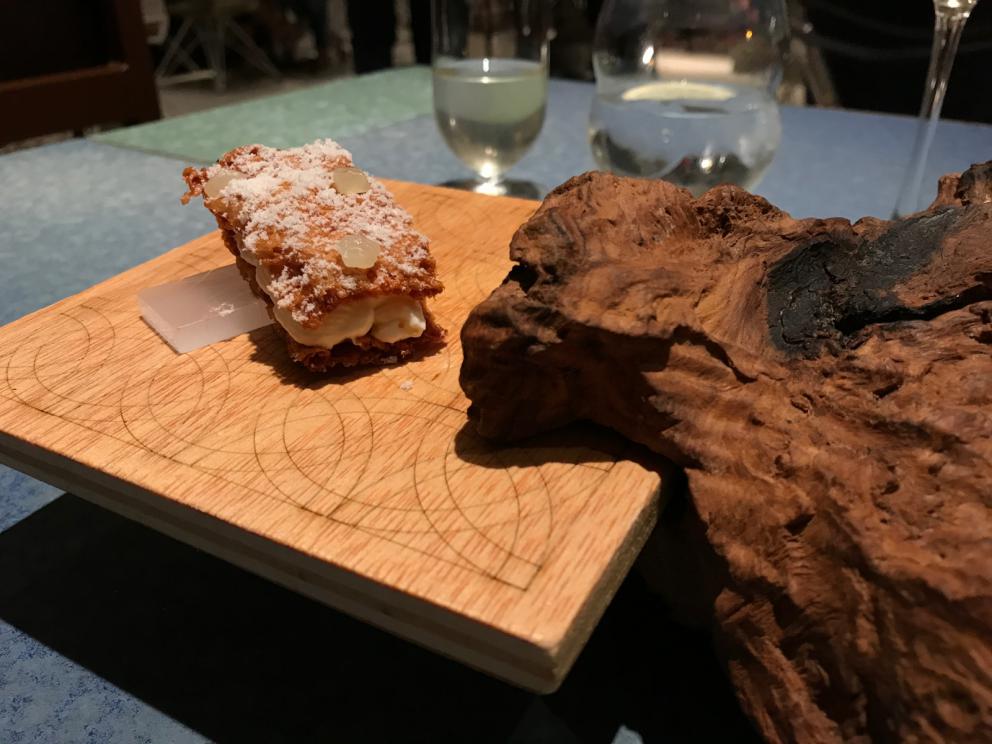 Galleria fotografica






L'inizio di un percorso meraviglioso: Lengua helada de pasión con ron, ossia una lingua di gatto gelata al rum, frutto della passione e menta piperita. Inizia il gioco di temperature









Rosa & lichis: poesia pura. Sferificazioni di acqua di rose (sui petali laterali) e finta mora ghiacciata di lichi









La remolacha que sale de tierra: insieme sorbetto e meringa di barbabietola









Panchino relleno de caviar beluga: uno dei piatti signature del Disfrutar. Si prepara una pasta per brioche con molta acqua e lievito. Viene collocata in un sifone e si ottiene una schiuma. Quindi si riempie il fondo di uno stampo circolare con questa schiuma, si aggiunge il caviale e una crema doppia panna, quindi ancora schiuma per coprire il tutto. Si immerge in una padella con olio a 180 gradi per 20 secondi. Ovviamente il caviale può essere sostituito da formaggi, tonno, sorbetti...









La preparazione al tavolo del Sidra casera ahumada al momento, un sidro di mele istantaneo: si versa sul ghiaccio secco una mistura di liquore e succo di mela e si lascia agire









Inizia il tributo alle noci. Qui il gheriglio, ricostruito, custodisce un quarto di noce, affumicata. E deliziosa. In pratica il guscio è stato aperto, senza romperlo; la noce è stata affumicata, poi rimessa al suo posto, il tutto richiuso









Ancora Cáscara de nuez: qui è un tripudio. Una noce tenera, senza pelle, l'altra verde col gheriglio e resa commestibile, infine l'ultima cotta e macerata nel ratafià, come abbiamo già spiegato nel pezzo. Il tutto con un filo di latte di noce e di olio di frutta secca. L'idea è: con un prodotto possiamo costruire all'infinito









Candy salado de nueces con mango, haba tonka y whisky: la bustina commestibile contiene caramello salato e noci, quindi il mango crudo e il profumo del whisky affumicato






