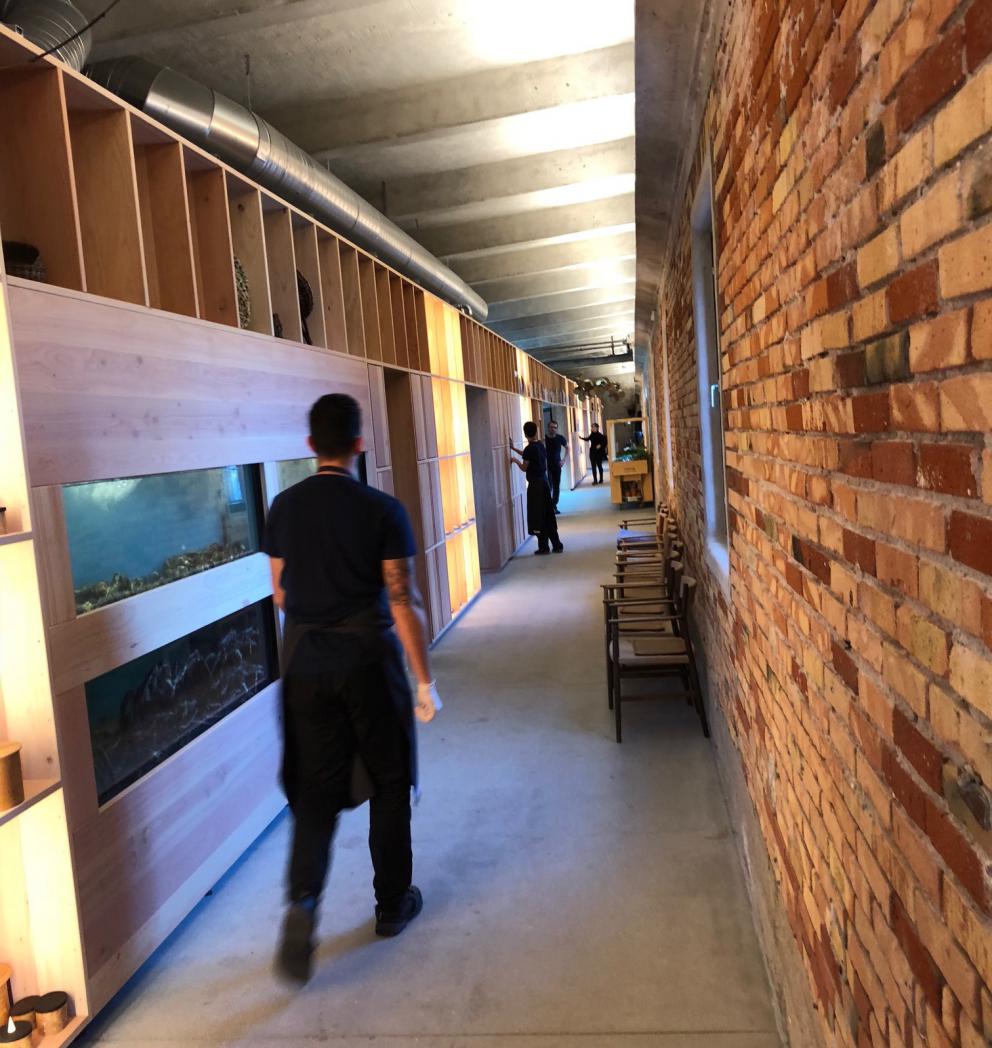 Photogallery






Noma 2.0 is in Christianshavn, the same neighbourhood as the first Noma. They’re 1.5 km apart, a 15 minutes’ walk. This picture shows the distance: to the right, there’s the warehouse of the old location (in Strandgade 93), to the left the smokestacks of Amager Bakke, the futuristic incinerator below which stands the new Noma (in Refshalevej 96)









Weather permitting, you can have a peaceful walk between the previous Noma to today’s Noma 









The new Noma is on an isthmus surrounded by canals. In the future they also want to reclaim some small parts for hydroponic farming









Bucolic scene with incinerator









Bikes left outside Noma. It’s the favourite means of transport among employees and interns









The long path taking you to the restaurant. The fence on the left shows how works are still in progress









On the two sides of the path there are the two new sections of the "Noma village", each with its specialty: grill, hot dishes, snacks, fermentations... In one month’s time, behind the fence we’ll have greenhouses, the test kitchen and the bread making area









To the left, before arriving at the restaurant, the future test kitchen. This will be run by Danish Mette Søberg with Riccardo Canella. "My first challenge?", reveals the latter, for a long time sous chef here, "is to work on the extraction of essential oils" 









The future Test Kitchen









The temporary gangway to the restaurant









Looking from the door to the restaurant, there’s a lake and the smokestacks puffing vapour from the Amager Bakke incinerator. It’s a futuristic project, both in terms of sustainability and architecture. It’s also known as Amager Slope or Copenhill, and its author is starchitect Bjarke Ingels, the same who designed the new Noma. Gradually opened in 2017, it transforms waste into electricity. The goal is to donate electricity to 62500 houses and hot water to 160000. It’s part of an ambitious project to transform Copenhagen into the first city in the world in terms of zero carbon dioxide emissions by 2025. By autumn this year, Amager Slope should open its ski slope, a climbing wall and a hiking track. You’ll be able to slalom on top of the incinerator









The windows from the dining room









Work is still in progress (photo taken on Thursday 22nd February 2018)









Traces of the old building, with barbwire. During WWII, they built bombs here









A view of the dining room at night (photo from Instagram/James Spreadbury)









The entrance to the restaurant









The usual ritual: a welcome from the entire staff, led by Rene Redzepi 









Behind the entrance, there are formaldehyde tanks with creatures from the abyss, shaped as in Damien Hirst’s works. The first image once you’re inside is to reproduce a Scandinavian village









The service kitchen is larger, more spacious and a completely open view from the dining room: "It’s the heart of our Scandinavian village", says Canella. There are 30 cooks working here now. 10 more, compared to the previous Noma









Large skylights above the cooks









There are currently more than 100 people working at Noma, of whom 63 are cooks - 26 employed, and 37 as interns









There’s fire in the kitchen, for the first time









On average, the dining room can host 40 people. "However", complains Redzepi, "there’s always someone who turns up with more people than the ones booked"









While the dining room is set, the outside space still need to be defined









The staff made the dining room decorations. There are no overly expensive designer objects









Dried fish









Seaweeds hanging from the ceiling









Dried octopus heads preserved in salt (with a balloon inside)














Bjarke Ingels and Redzepi’s plan included the wish to recreate a Danish farm









The luminous private dining room









The counter in the dining room. They drew the beams from the canals around the restaurant














The mise en place, bare and strictly without tablecloths









Water jug, candle, flower vase









A warm cloth, to begin with









Australian James Spreadbury, restaurant manager and partner at Noma









Welcome drink: Champagne extra brut Blanc d'Argile from Domaine Vouette et Sorbée









Sea Snail broth. The welcome dish at Noma is, as usual, a hot “soup”









Stefano Ferrano, from Torino, presents the following dish. There’s always a large Italian colony at Noma









Venus clams. Molluscs from Limfjord (Denmark) mixed with decorative clams, typical of Noma. Beside them, shells with blackcurrant oil and “Danish curry”, made with toasted coriander seeds, fennel and fennel seeds









The lid above the following dish. The mussels are not edible









Best of the mussel. Mussels open in a pan with water of fermented barley. «We recreate the mussel», says Canella, «using just the flaps, the best part». The paste is made with scraps from the mussel, cooked in smoked butter









The next dish is conceived and served by Riccardo Canella, the Paduan sous chef who conquered Redzepi, here with dining room intern Feline Hansen









Dried fruits and shrimps. In this case, the heads are not a decoration, but you must suck them –best not eat them because of the bones: they’re filled with a lovely prawn cream. The small crustaceans are still alive when they arrive on a ship straight from the Norwegian fjords









Inside, under the prawn broth skin, there’s fruits and vegetable preserved from the previous summer with raw prawns and gooseberry sauce with blackcurrant oil









How about beverages? There are three options, as usual: wine pairing (6 glasses plus a beer plus sake, 150 euros), juice pairing (juices and extracts, 110 euros) or a choice from the list. They recommend Champagne Chut... Libre from Val'Frison pour Dominique Derain, 50% Pinot Noir, 50% Chardonnay created by a couple who met at the old Noma. Well bodied, it will be a good match throughout the meal









As usual, the wine list starts with Champagne: the cheapest is 1400 crowns (190 euros)









White wines begin with labels from cold climates: first Austria, increasingly popular for its natural wines, then Germany, then all the others









How about Italy? Few names, among the white wines, from North and South









A dozen red/orange wines









Sea star, that is to say Cured trout roe and eggs, the emblem dish of this new era. They recommend moving the teaspoon from the heart to the edges of the tentacles. Aesthetics win over taste









Jellyfish. The jellyfish gel in the middle is in fact a clarified broth of calamari and recalls the texture of jellyfish. "We tried to cook jellyfish in 300 different ways but none was convincing so far". All around, pickled seaweed. The gel is almost tasteless, it serves to clean the palate after the pickles









Rene Redzepi himself presents the content of the first Seafood platter.









French style service with a small plate below for the empty shells









It’s made of two (per two) pieces: queen clam and mahogany clam









The Queen Clam is a very small variety of Norwegian scallop, seasoned with a vegetal reduction made with cucumber and peas miso. The red tip is the coral. "You should eat it using the top shell ", recommends Redzepi









The Mahogany clam is a centennial clam from the North Sea, very popular in Denmark and Iceland. «You can tell the age by the number of rings, like with trees», says Redzepi, «In 2007 they found one that was 450 years old. We’ve had it in the menu for a decade or so». The razor clam shell serves as teaspoon









Inside, there’s obviously not just a bare Mahogany. «We open it when the client arrives», says Canella, «remove the entrails and then slice it so as to preserve its firm texture». It’s seasoned with stir-fried gooseberry, capers of blackcurrants and blackcurrant sprouts preserved in vinegar. The sauce is made with mussel water









A note on the chairs: they’re more minimalistic. They’re no longer covered in sheepskin or leather from other Danish animals, in the style of Noma 1.0. The most significant element is the napkin: if you go to the toilet, they no longer replace it with a new one. There’s the old one, tied to the chair. "This is sustainability", they explain









The second seafood platter. It’s made of Sea cucumber and sour cream in various textures, including «chicharrones» (at 9 o’clock), sea urchins (at 12 and 3) and gigas oyster (at 6)









Sea urchins pressed in fresh cream and pumpkin seeds









Giga Oyster, a huge oyster from the Pacific, quickly steamed and garnished with pickles. Noma only reserved one thousand of these. In the menu until available









The following dish, off the menu, is again from Canella: horse mussel ragout, rare specimen of which 30 arrive at 'Noma each week









They cook the mussel as if it were kidney, in a sort of Bolognese sauce but with ginger. Ginger? "Yes, we’ve decided to include it, as with other spices, after our Mexican experience"









Another Italian presents a dish, Edoardo Fiaschi from Prato, at Noma for 3 years now









Squid in seaweed butter. An almost neglected Danish squid lightly seared in fermented koji oil, rolled and seasoned with seaweed butter and served on sticks of blackcurrant that widen its aromas. Formidable and beautiful









The following dish is inside a nice bee wax container. It’s made with balloons covered multiple times in bee wax. «We spent weeks making them. We’ve made thousands». They’re disposable...









Sea snail and roses. They recommend to: "Eat it keeping the bee wax on your hands "









Sea snail. Another small nibble from the top part of the sea snail, lightly warmed up in water and served on a reduction of lemon thyme









A sea snail toothpick, initially carved by Redzepi himself









Head of the cod, (right), the real main course at Noma









Another rather laborious recipe. «It takes half an hour just to separate the head. We remove the skin, the collagen, we cut mandibles, tongue, cheek and the part behind. We rinse it in water, spices, koji and cook it in the yakitori with a glaze of mushrooms and spiced fennel broth»









You can garnish the cod as you choose, with a paste of ants (top right corner), a slightly spicy emulsion of koji oil, water and horseradish sauce (left) and Danish curry (bottom)









On the side of the cod, there’s also wild garlic seasoned with smoked butter and roasted yeast. Intense flavour









Cod bones after the tasting









An interlocutory snack made of cod cheek









Pickled vegetables and arctic herbs. The only vegetable dish in the menu, marks the passage from savoury to sweet dishes. Between June and August 2018 the menu at Noma will be 100% vegetarian









Preparation time: half an hour! A challenge for the person making it









Mussels appear once again, a classic emblem









This time it’s a dessert in the shape of a small sandwich. Pear and roasted kelp ice cream 









Cloudberries and pinecones. A dessert that continues Redzepi’s saga of unsweet sweets: cloudberries, pinecones preserved in sugar, yogurt snow (by Italian Jessica Natali) and a sea snail made with cloudberry sorbet









Filtered coffee made with stolen kenyoti seeds farmed in Honduras by a Norwegian guy. Italian sommelier Francesca Niro tells us this story. «In Denmark», she says, «coffee is not a final act»









Sugar kelp tart. Tartelletta di alga kelp con pralinato di pino (sul modello di quello di mandorle, autore Canella), panna e crisp di ostrica









Sugar kelp tart. Jessica Natali, 23, from the March, has been at Noma for 4 years now









Natali introduces the last dish, Plankton cake









It’s Redzepi’s tribute to Andalusian chef Angel Leon, the chef who brought the abyss of the sea on fine dining tables. A final trivia fact at the end of the meal: we were never served bread, a historic strongpoint at Noma. "There’s no need for bread in this menu", said Redzepi






