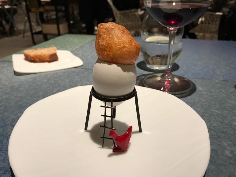 Galleria fotografica






L'inizio di un percorso meraviglioso: Lengua helada de pasión con ron, ossia una lingua di gatto gelata al rum, frutto della passione e menta piperita. Inizia il gioco di temperature









Rosa & lichis: poesia pura. Sferificazioni di acqua di rose (sui petali laterali) e finta mora ghiacciata di lichi









La remolacha que sale de tierra: insieme sorbetto e meringa di barbabietola









Panchino relleno de caviar beluga: uno dei piatti signature del Disfrutar. Si prepara una pasta per brioche con molta acqua e lievito. Viene collocata in un sifone e si ottiene una schiuma. Quindi si riempie il fondo di uno stampo circolare con questa schiuma, si aggiunge il caviale e una crema doppia panna, quindi ancora schiuma per coprire il tutto. Si immerge in una padella con olio a 180 gradi per 20 secondi. Ovviamente il caviale può essere sostituito da formaggi, tonno, sorbetti...









La preparazione al tavolo del Sidra casera ahumada al momento, un sidro di mele istantaneo: si versa sul ghiaccio secco una mistura di liquore e succo di mela e si lascia agire









Inizia il tributo alle noci. Qui il gheriglio, ricostruito, custodisce un quarto di noce, affumicata. E deliziosa. In pratica il guscio è stato aperto, senza romperlo; la noce è stata affumicata, poi rimessa al suo posto, il tutto richiuso









Ancora Cáscara de nuez: qui è un tripudio. Una noce tenera, senza pelle, l'altra verde col gheriglio e resa commestibile, infine l'ultima cotta e macerata nel ratafià, come abbiamo già spiegato nel pezzo. Il tutto con un filo di latte di noce e di olio di frutta secca. L'idea è: con un prodotto possiamo costruire all'infinito









Candy salado de nueces con mango, haba tonka y whisky: la bustina commestibile contiene caramello salato e noci, quindi il mango crudo e il profumo del whisky affumicato









Milhojas de idiazábal, millefoglie di idiazábal, un formaggio basco. Sterzata salata dopo una prima parte di degustazione in cui prevalevano le note dolci (a esaltare anche il caviale del Panchino). In generale, sono tutti piatti che superano la tradizionale distinzione dolce/salato









"Hostia" de flor del mandarino: la finta ostia è di ovulato, racchiude essenza di fiore di mandarino. Un piatto che colpisce il cuore









La Gilda del Disfrutar. La gilda è il classico pincho che si serve nei Paesi Baschi, a base di olive e acciughe. Qui abbiamo le celebri false olive di Adrià, croccanti fuori (burro di cacao) e liquide all'interno. Poi sgombro marinato, semi di pepe basco e la loro crema









Sandwich de gazpacho con guarnición olorosa de vinagre de Jerez: qui il falso pane ghiacciato (sono meringhe di pomodoro secco) racchiude una farcitura in cui emergono le note acide e aromatiche dell'aceto di Jerez a esaltare il classico aroma del gazpacho andaluso









Almendras "supertiernas" en vinagreta: al Disfrutar giocano molto con la frutta secca, qui mandorle ammorbidite o croccanti e accompagnate da aromi di vaniglia, aglio, olio, vinaigrette... Altro capolavoro






