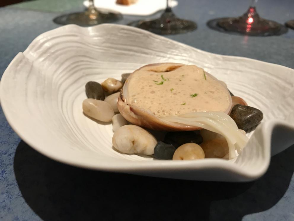 Galleria fotografica






L'inizio di un percorso meraviglioso: Lengua helada de pasión con ron, ossia una lingua di gatto gelata al rum, frutto della passione e menta piperita. Inizia il gioco di temperature









Rosa & lichis: poesia pura. Sferificazioni di acqua di rose (sui petali laterali) e finta mora ghiacciata di lichi









La remolacha que sale de tierra: insieme sorbetto e meringa di barbabietola









Panchino relleno de caviar beluga: uno dei piatti signature del Disfrutar. Si prepara una pasta per brioche con molta acqua e lievito. Viene collocata in un sifone e si ottiene una schiuma. Quindi si riempie il fondo di uno stampo circolare con questa schiuma, si aggiunge il caviale e una crema doppia panna, quindi ancora schiuma per coprire il tutto. Si immerge in una padella con olio a 180 gradi per 20 secondi. Ovviamente il caviale può essere sostituito da formaggi, tonno, sorbetti...









La preparazione al tavolo del Sidra casera ahumada al momento, un sidro di mele istantaneo: si versa sul ghiaccio secco una mistura di liquore e succo di mela e si lascia agire









Inizia il tributo alle noci. Qui il gheriglio, ricostruito, custodisce un quarto di noce, affumicata. E deliziosa. In pratica il guscio è stato aperto, senza romperlo; la noce è stata affumicata, poi rimessa al suo posto, il tutto richiuso









Ancora Cáscara de nuez: qui è un tripudio. Una noce tenera, senza pelle, l'altra verde col gheriglio e resa commestibile, infine l'ultima cotta e macerata nel ratafià, come abbiamo già spiegato nel pezzo. Il tutto con un filo di latte di noce e di olio di frutta secca. L'idea è: con un prodotto possiamo costruire all'infinito









Candy salado de nueces con mango, haba tonka y whisky: la bustina commestibile contiene caramello salato e noci, quindi il mango crudo e il profumo del whisky affumicato









Milhojas de idiazábal, millefoglie di idiazábal, un formaggio basco. Sterzata salata dopo una prima parte di degustazione in cui prevalevano le note dolci (a esaltare anche il caviale del Panchino). In generale, sono tutti piatti che superano la tradizionale distinzione dolce/salato









"Hostia" de flor del mandarino: la finta ostia è di ovulato, racchiude essenza di fiore di mandarino. Un piatto che colpisce il cuore









La Gilda del Disfrutar. La gilda è il classico pincho che si serve nei Paesi Baschi, a base di olive e acciughe. Qui abbiamo le celebri false olive di Adrià, croccanti fuori (burro di cacao) e liquide all'interno. Poi sgombro marinato, semi di pepe basco e la loro crema









Sandwich de gazpacho con guarnición olorosa de vinagre de Jerez: qui il falso pane ghiacciato (sono meringhe di pomodoro secco) racchiude una farcitura in cui emergono le note acide e aromatiche dell'aceto di Jerez a esaltare il classico aroma del gazpacho andaluso









Almendras "supertiernas" en vinagreta: al Disfrutar giocano molto con la frutta secca, qui mandorle ammorbidite o croccanti e accompagnate da aromi di vaniglia, aglio, olio, vinaigrette... Altro capolavoro









Yema de huevo crujiente con gelatina caliente de setas: una crema d'uovo in tempura, croccante fuori e liquida dentro, sopra un gel di funghi racchiuso nel guscio dell'uovo stesso. «Per noi è un classico - ci dicono - Ma sempre molto difficile da gestire»









Piatto spettacolare e gentile, Tatin de foie-gras y maíz multiesférico: tutto giocato su un equilibrio in cui le note dolci sono spinte al limite. La tecnica è quella della multisferificazione, con gel di glutammato a chiudere la partita









Ceviche en deconstrucción: leche de tigre, emulsione di pesce, olio di coriandolo e sorbetto di zucca e ajì. Un classico del Disfrutar

 









Questa è la cartilagine del muso del salmone...









...protagonista di quest'altro piatto, nuovissimo: il collagene del muso del salmone con le sue uova e salsa di acetosella. Wow!









Altra novità, presentata a Gastronomika, è la Costilla de salmón con mojo di estragón. Le costolette di salmone, ottenute una a una sfilettando con attenzione le lische con la polpa attorno, sono accompagnate da mojo di dragoncello e uova di salmone









Conserva de navajas a la sal: le navajas sono state lasciate macerare per un giorno con alghe nel frigorifero, poi 5 minuti al forno. Sono molluschi chiamati "guscio rasoio", tassonomicamente Ensis arcuatus, simili ai cannolicchi. Qui con olio e aceto di Jerez 25 anni









Ensalada líquida, non serve traduzione...









...accompagnata da Polvorón de tomate y caviaroli de arbequina. Il polvorón è un classico dolce spagnolo di Natale, molto friabile, in genere fatto di farina, zucchero, latte e mandorle. Qui è di pomodoro e accompagnato da caviaroli di oliva arbequina: il Caviaroli è di una ditta catalana che sferifica varie tipologie di olio evo, anche aromatizzato, ce n'è anche una a base di tartufo Tartuflanghe









Tre piatti che raccontano il suquet, tipica salsa a base di pesce. Qui Noodles de espardeñas (le rare “lingue di mare”, in tassonomia stichopus regalis) en suquet









Langostino (ossia gamberone) en suquet, con gnocchi di patata, aria di prezzemolo, crema di zafferano e patata. Sul fondo si vede anche il Capucchino de suquet









Finale salato a base di piccione: qui il suo consommé con armagnac, dragoncello e arancia









Bombon di piccione e foie e foglia d'argento






