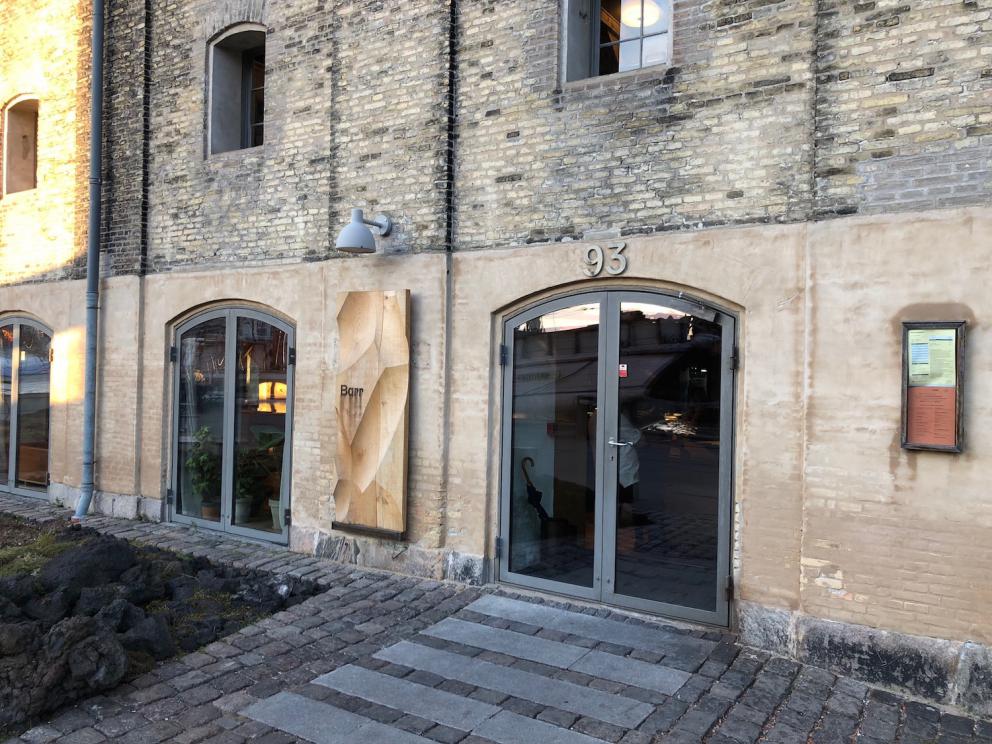 Photogallery






Noma 2.0 is in Christianshavn, the same neighbourhood as the first Noma. They’re 1.5 km apart, a 15 minutes’ walk. This picture shows the distance: to the right, there’s the warehouse of the old location (in Strandgade 93), to the left the smokestacks of Amager Bakke, the futuristic incinerator below which stands the new Noma (in Refshalevej 96)









Weather permitting, you can have a peaceful walk between the previous Noma to today’s Noma 









The new Noma is on an isthmus surrounded by canals. In the future they also want to reclaim some small parts for hydroponic farming









Bucolic scene with incinerator









Bikes left outside Noma. It’s the favourite means of transport among employees and interns









The long path taking you to the restaurant. The fence on the left shows how works are still in progress









On the two sides of the path there are the two new sections of the "Noma village", each with its specialty: grill, hot dishes, snacks, fermentations... In one month’s time, behind the fence we’ll have greenhouses, the test kitchen and the bread making area









To the left, before arriving at the restaurant, the future test kitchen. This will be run by Danish Mette Søberg with Riccardo Canella. "My first challenge?", reveals the latter, for a long time sous chef here, "is to work on the extraction of essential oils" 









The future Test Kitchen









The temporary gangway to the restaurant









Looking from the door to the restaurant, there’s a lake and the smokestacks puffing vapour from the Amager Bakke incinerator. It’s a futuristic project, both in terms of sustainability and architecture. It’s also known as Amager Slope or Copenhill, and its author is starchitect Bjarke Ingels, the same who designed the new Noma. Gradually opened in 2017, it transforms waste into electricity. The goal is to donate electricity to 62500 houses and hot water to 160000. It’s part of an ambitious project to transform Copenhagen into the first city in the world in terms of zero carbon dioxide emissions by 2025. By autumn this year, Amager Slope should open its ski slope, a climbing wall and a hiking track. You’ll be able to slalom on top of the incinerator









The windows from the dining room









Work is still in progress (photo taken on Thursday 22nd February 2018)









Traces of the old building, with barbwire. During WWII, they built bombs here









A view of the dining room at night (photo from Instagram/James Spreadbury)









The entrance to the restaurant









The usual ritual: a welcome from the entire staff, led by Rene Redzepi 









Behind the entrance, there are formaldehyde tanks with creatures from the abyss, shaped as in Damien Hirst’s works. The first image once you’re inside is to reproduce a Scandinavian village









The service kitchen is larger, more spacious and a completely open view from the dining room: "It’s the heart of our Scandinavian village", says Canella. There are 30 cooks working here now. 10 more, compared to the previous Noma









Large skylights above the cooks









There are currently more than 100 people working at Noma, of whom 63 are cooks - 26 employed, and 37 as interns









There’s fire in the kitchen, for the first time









On average, the dining room can host 40 people. "However", complains Redzepi, "there’s always someone who turns up with more people than the ones booked"









While the dining room is set, the outside space still need to be defined









The staff made the dining room decorations. There are no overly expensive designer objects









Dried fish









Seaweeds hanging from the ceiling









Dried octopus heads preserved in salt (with a balloon inside)














Bjarke Ingels and Redzepi’s plan included the wish to recreate a Danish farm









The luminous private dining room









The counter in the dining room. They drew the beams from the canals around the restaurant














The mise en place, bare and strictly without tablecloths









Water jug, candle, flower vase









A warm cloth, to begin with









Australian James Spreadbury, restaurant manager and partner at Noma









Welcome drink: Champagne extra brut Blanc d'Argile from Domaine Vouette et Sorbée









Sea Snail broth. The welcome dish at Noma is, as usual, a hot “soup”









Stefano Ferrano, from Torino, presents the following dish. There’s always a large Italian colony at Noma









Venus clams. Molluscs from Limfjord (Denmark) mixed with decorative clams, typical of Noma. Beside them, shells with blackcurrant oil and “Danish curry”, made with toasted coriander seeds, fennel and fennel seeds









The lid above the following dish. The mussels are not edible









Best of the mussel. Mussels open in a pan with water of fermented barley. «We recreate the mussel», says Canella, «using just the flaps, the best part». The paste is made with scraps from the mussel, cooked in smoked butter









The next dish is conceived and served by Riccardo Canella, the Paduan sous chef who conquered Redzepi, here with dining room intern Feline Hansen









Dried fruits and shrimps. In this case, the heads are not a decoration, but you must suck them –best not eat them because of the bones: they’re filled with a lovely prawn cream. The small crustaceans are still alive when they arrive on a ship straight from the Norwegian fjords









Inside, under the prawn broth skin, there’s fruits and vegetable preserved from the previous summer with raw prawns and gooseberry sauce with blackcurrant oil









How about beverages? There are three options, as usual: wine pairing (6 glasses plus a beer plus sake, 150 euros), juice pairing (juices and extracts, 110 euros) or a choice from the list. They recommend Champagne Chut... Libre from Val'Frison pour Dominique Derain, 50% Pinot Noir, 50% Chardonnay created by a couple who met at the old Noma. Well bodied, it will be a good match throughout the meal









As usual, the wine list starts with Champagne: the cheapest is 1400 crowns (190 euros)









White wines begin with labels from cold climates: first Austria, increasingly popular for its natural wines, then Germany, then all the others









How about Italy? Few names, among the white wines, from North and South









A dozen red/orange wines









Sea star, that is to say Cured trout roe and eggs, the emblem dish of this new era. They recommend moving the teaspoon from the heart to the edges of the tentacles. Aesthetics win over taste









Jellyfish. The jellyfish gel in the middle is in fact a clarified broth of calamari and recalls the texture of jellyfish. "We tried to cook jellyfish in 300 different ways but none was convincing so far". All around, pickled seaweed. The gel is almost tasteless, it serves to clean the palate after the pickles









Rene Redzepi himself presents the content of the first Seafood platter.









French style service with a small plate below for the empty shells









It’s made of two (per two) pieces: queen clam and mahogany clam









The Queen Clam is a very small variety of Norwegian scallop, seasoned with a vegetal reduction made with cucumber and peas miso. The red tip is the coral. "You should eat it using the top shell ", recommends Redzepi









The Mahogany clam is a centennial clam from the North Sea, very popular in Denmark and Iceland. «You can tell the age by the number of rings, like with trees», says Redzepi, «In 2007 they found one that was 450 years old. We’ve had it in the menu for a decade or so». The razor clam shell serves as teaspoon









Inside, there’s obviously not just a bare Mahogany. «We open it when the client arrives», says Canella, «remove the entrails and then slice it so as to preserve its firm texture». It’s seasoned with stir-fried gooseberry, capers of blackcurrants and blackcurrant sprouts preserved in vinegar. The sauce is made with mussel water









A note on the chairs: they’re more minimalistic. They’re no longer covered in sheepskin or leather from other Danish animals, in the style of Noma 1.0. The most significant element is the napkin: if you go to the toilet, they no longer replace it with a new one. There’s the old one, tied to the chair. "This is sustainability", they explain









The second seafood platter. It’s made of Sea cucumber and sour cream in various textures, including «chicharrones» (at 9 o’clock), sea urchins (at 12 and 3) and gigas oyster (at 6)









Sea urchins pressed in fresh cream and pumpkin seeds









Giga Oyster, a huge oyster from the Pacific, quickly steamed and garnished with pickles. Noma only reserved one thousand of these. In the menu until available









The following dish, off the menu, is again from Canella: horse mussel ragout, rare specimen of which 30 arrive at 'Noma each week









They cook the mussel as if it were kidney, in a sort of Bolognese sauce but with ginger. Ginger? "Yes, we’ve decided to include it, as with other spices, after our Mexican experience"









Another Italian presents a dish, Edoardo Fiaschi from Prato, at Noma for 3 years now









Squid in seaweed butter. An almost neglected Danish squid lightly seared in fermented koji oil, rolled and seasoned with seaweed butter and served on sticks of blackcurrant that widen its aromas. Formidable and beautiful









The following dish is inside a nice bee wax container. It’s made with balloons covered multiple times in bee wax. «We spent weeks making them. We’ve made thousands». They’re disposable...









Sea snail and roses. They recommend to: "Eat it keeping the bee wax on your hands "









Sea snail. Another small nibble from the top part of the sea snail, lightly warmed up in water and served on a reduction of lemon thyme









A sea snail toothpick, initially carved by Redzepi himself









Head of the cod, (right), the real main course at Noma









Another rather laborious recipe. «It takes half an hour just to separate the head. We remove the skin, the collagen, we cut mandibles, tongue, cheek and the part behind. We rinse it in water, spices, koji and cook it in the yakitori with a glaze of mushrooms and spiced fennel broth»









You can garnish the cod as you choose, with a paste of ants (top right corner), a slightly spicy emulsion of koji oil, water and horseradish sauce (left) and Danish curry (bottom)









On the side of the cod, there’s also wild garlic seasoned with smoked butter and roasted yeast. Intense flavour









Cod bones after the tasting









An interlocutory snack made of cod cheek









Pickled vegetables and arctic herbs. The only vegetable dish in the menu, marks the passage from savoury to sweet dishes. Between June and August 2018 the menu at Noma will be 100% vegetarian









Preparation time: half an hour! A challenge for the person making it









Mussels appear once again, a classic emblem









This time it’s a dessert in the shape of a small sandwich. Pear and roasted kelp ice cream 









Cloudberries and pinecones. A dessert that continues Redzepi’s saga of unsweet sweets: cloudberries, pinecones preserved in sugar, yogurt snow (by Italian Jessica Natali) and a sea snail made with cloudberry sorbet









Filtered coffee made with stolen kenyoti seeds farmed in Honduras by a Norwegian guy. Italian sommelier Francesca Niro tells us this story. «In Denmark», she says, «coffee is not a final act»









Sugar kelp tart. Tartelletta di alga kelp con pralinato di pino (sul modello di quello di mandorle, autore Canella), panna e crisp di ostrica









Sugar kelp tart. Jessica Natali, 23, from the March, has been at Noma for 4 years now









Natali introduces the last dish, Plankton cake









It’s Redzepi’s tribute to Andalusian chef Angel Leon, the chef who brought the abyss of the sea on fine dining tables. A final trivia fact at the end of the meal: we were never served bread, a historic strongpoint at Noma. "There’s no need for bread in this menu", said Redzepi









With Canella we walk the very long corridor that starts from the opposite side of the room, right after the entrance









It’s the rationalised and enlarged equivalent of the previous Noma’s first floor. Dozens of guys are making the pre-preparations









Canella with Ali Sonko, Noma’s famous kitchen hand from Gambia who then became partner









Sea cucumbers and huge Artic crabs swim in the water tanks














Ants on a shrimp, the emblem of Noma’s pop-up in Tokyo














The new equipment includes a sonicator for emulsions, a Rotovapor, essential oil extractors. Natural extraction, like that of perfumes, is an idea that Canella would like to develop in all possible ways, following the example of Alajmo









Temporary location for wild herbs









The staff area









Final relax in the lounge next to the dining room, much larger and more luminous than the previous one









They give us the bill: a total of 3250 crowns (436 euros), including the 2250 Danish crown menu (302 euros), already paid when booking 3 months ago, 50 crowns for water (6.50 euros), 700 for champagne (half of 1400 crowns, that is to say 190 euros), 175 (23,50) for the welcome Champagne glass and 75 (10 euros) for coffee. Ten percent of the places are reserved for students at a shared table: they pay a special fee of 1000 crowns (134 euros) for the menu including either the wine or juice pairing. For reservations click here









How about the old Noma? It’s been replaced by Barr, serving traditional Danish classics paired with craft beer and aquavit






