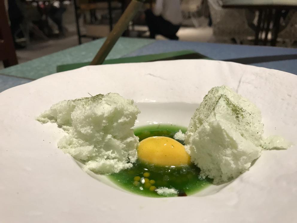 Galleria fotografica






L'inizio di un percorso meraviglioso: Lengua helada de pasión con ron, ossia una lingua di gatto gelata al rum, frutto della passione e menta piperita. Inizia il gioco di temperature









Rosa & lichis: poesia pura. Sferificazioni di acqua di rose (sui petali laterali) e finta mora ghiacciata di lichi









La remolacha que sale de tierra: insieme sorbetto e meringa di barbabietola









Panchino relleno de caviar beluga: uno dei piatti signature del Disfrutar. Si prepara una pasta per brioche con molta acqua e lievito. Viene collocata in un sifone e si ottiene una schiuma. Quindi si riempie il fondo di uno stampo circolare con questa schiuma, si aggiunge il caviale e una crema doppia panna, quindi ancora schiuma per coprire il tutto. Si immerge in una padella con olio a 180 gradi per 20 secondi. Ovviamente il caviale può essere sostituito da formaggi, tonno, sorbetti...









La preparazione al tavolo del Sidra casera ahumada al momento, un sidro di mele istantaneo: si versa sul ghiaccio secco una mistura di liquore e succo di mela e si lascia agire









Inizia il tributo alle noci. Qui il gheriglio, ricostruito, custodisce un quarto di noce, affumicata. E deliziosa. In pratica il guscio è stato aperto, senza romperlo; la noce è stata affumicata, poi rimessa al suo posto, il tutto richiuso









Ancora Cáscara de nuez: qui è un tripudio. Una noce tenera, senza pelle, l'altra verde col gheriglio e resa commestibile, infine l'ultima cotta e macerata nel ratafià, come abbiamo già spiegato nel pezzo. Il tutto con un filo di latte di noce e di olio di frutta secca. L'idea è: con un prodotto possiamo costruire all'infinito









Candy salado de nueces con mango, haba tonka y whisky: la bustina commestibile contiene caramello salato e noci, quindi il mango crudo e il profumo del whisky affumicato









Milhojas de idiazábal, millefoglie di idiazábal, un formaggio basco. Sterzata salata dopo una prima parte di degustazione in cui prevalevano le note dolci (a esaltare anche il caviale del Panchino). In generale, sono tutti piatti che superano la tradizionale distinzione dolce/salato









"Hostia" de flor del mandarino: la finta ostia è di ovulato, racchiude essenza di fiore di mandarino. Un piatto che colpisce il cuore









La Gilda del Disfrutar. La gilda è il classico pincho che si serve nei Paesi Baschi, a base di olive e acciughe. Qui abbiamo le celebri false olive di Adrià, croccanti fuori (burro di cacao) e liquide all'interno. Poi sgombro marinato, semi di pepe basco e la loro crema









Sandwich de gazpacho con guarnición olorosa de vinagre de Jerez: qui il falso pane ghiacciato (sono meringhe di pomodoro secco) racchiude una farcitura in cui emergono le note acide e aromatiche dell'aceto di Jerez a esaltare il classico aroma del gazpacho andaluso









Almendras "supertiernas" en vinagreta: al Disfrutar giocano molto con la frutta secca, qui mandorle ammorbidite o croccanti e accompagnate da aromi di vaniglia, aglio, olio, vinaigrette... Altro capolavoro









Yema de huevo crujiente con gelatina caliente de setas: una crema d'uovo in tempura, croccante fuori e liquida dentro, sopra un gel di funghi racchiuso nel guscio dell'uovo stesso. «Per noi è un classico - ci dicono - Ma sempre molto difficile da gestire»









Piatto spettacolare e gentile, Tatin de foie-gras y maíz multiesférico: tutto giocato su un equilibrio in cui le note dolci sono spinte al limite. La tecnica è quella della multisferificazione, con gel di glutammato a chiudere la partita









Ceviche en deconstrucción: leche de tigre, emulsione di pesce, olio di coriandolo e sorbetto di zucca e ajì. Un classico del Disfrutar

 









Questa è la cartilagine del muso del salmone...









...protagonista di quest'altro piatto, nuovissimo: il collagene del muso del salmone con le sue uova e salsa di acetosella. Wow!









Altra novità, presentata a Gastronomika, è la Costilla de salmón con mojo di estragón. Le costolette di salmone, ottenute una a una sfilettando con attenzione le lische con la polpa attorno, sono accompagnate da mojo di dragoncello e uova di salmone









Conserva de navajas a la sal: le navajas sono state lasciate macerare per un giorno con alghe nel frigorifero, poi 5 minuti al forno. Sono molluschi chiamati "guscio rasoio", tassonomicamente Ensis arcuatus, simili ai cannolicchi. Qui con olio e aceto di Jerez 25 anni









Ensalada líquida, non serve traduzione...









...accompagnata da Polvorón de tomate y caviaroli de arbequina. Il polvorón è un classico dolce spagnolo di Natale, molto friabile, in genere fatto di farina, zucchero, latte e mandorle. Qui è di pomodoro e accompagnato da caviaroli di oliva arbequina: il Caviaroli è di una ditta catalana che sferifica varie tipologie di olio evo, anche aromatizzato, ce n'è anche una a base di tartufo Tartuflanghe









Tre piatti che raccontano il suquet, tipica salsa a base di pesce. Qui Noodles de espardeñas (le rare “lingue di mare”, in tassonomia stichopus regalis) en suquet









Langostino (ossia gamberone) en suquet, con gnocchi di patata, aria di prezzemolo, crema di zafferano e patata. Sul fondo si vede anche il Capucchino de suquet









Finale salato a base di piccione: qui il suo consommé con armagnac, dragoncello e arancia









Bombon di piccione e foie e foglia d'argento









Laksa de pichón. La laksa è una popolare zuppa di Singapore, speziata, con cocco, lime e citronella. Qui ccon riduzione di piccione e fideuà









Pichón Pibil con abrigo de màiz y trufa de verano: il pibil è una cottura tradizionale maya, sotto la cenere. Il piccione è coperto da un "cappotto" nero (abrigo) di mais e accompagnato da tartufo






